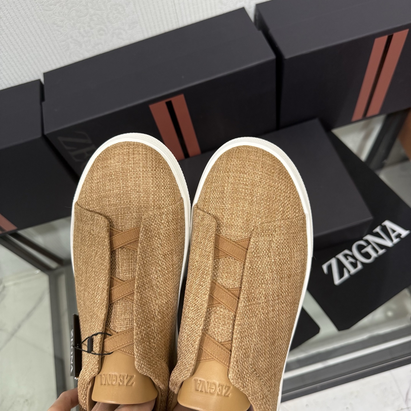 Zegna/杰尼亚 SECONDSKIN Triple Stitch&trade; 休闲运动鞋，帆布系列
这款低帮运动鞋的鞋面光滑柔软。饰以标志性三重交叉松紧细节，致敬品牌精裁夹克的手工缝制工艺。设计轻盈，与白色橡胶鞋底相得益彰，专为快节奏的生活方式打造。这款鞋汲取手套制作灵感，融汇世代工匠经验智慧，选用新西兰顶级小牛皮制作，成就轻盈质地，精致衬里结合非凡韧性。带来独一无二的贴合感。非常轻盈的橡胶外底上点缀双条纹 Logo 运动细节，以超轻结构重新诠释标志性鞋款。领口部位鹿皮面料反车做法，无内裡车中底套楦做法。易穿脱套脚交叉松紧带和 3D&ldquo;波纹&rdquo;设计。鞋舌热压品牌名称。
后跟加贴 TPU 双条纹品牌 Logo 饰条，鞋身空胶做法，周圈加车大底缝线。轻盈的高弹力橡胶外底背面和可拆卸脚床饰 Zegna 标识，为这款运动鞋增添现代动感气息。
皮鞋码数:39/40/41/42/43/44/45/46/47 
专柜包装，现货