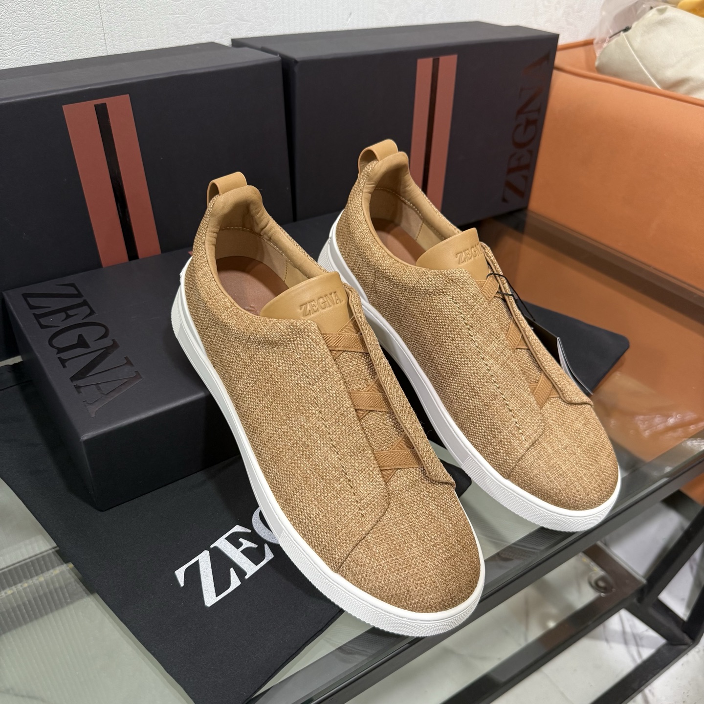 Zegna/杰尼亚 SECONDSKIN Triple Stitch&trade; 休闲运动鞋，帆布系列
这款低帮运动鞋的鞋面光滑柔软。饰以标志性三重交叉松紧细节，致敬品牌精裁夹克的手工缝制工艺。设计轻盈，与白色橡胶鞋底相得益彰，专为快节奏的生活方式打造。这款鞋汲取手套制作灵感，融汇世代工匠经验智慧，选用新西兰顶级小牛皮制作，成就轻盈质地，精致衬里结合非凡韧性。带来独一无二的贴合感。非常轻盈的橡胶外底上点缀双条纹 Logo 运动细节，以超轻结构重新诠释标志性鞋款。领口部位鹿皮面料反车做法，无内裡车中底套楦做法。易穿脱套脚交叉松紧带和 3D&ldquo;波纹&rdquo;设计。鞋舌热压品牌名称。
后跟加贴 TPU 双条纹品牌 Logo 饰条，鞋身空胶做法，周圈加车大底缝线。轻盈的高弹力橡胶外底背面和可拆卸脚床饰 Zegna 标识，为这款运动鞋增添现代动感气息。
皮鞋码数:39/40/41/42/43/44/45/46/47 
专柜包装，现货