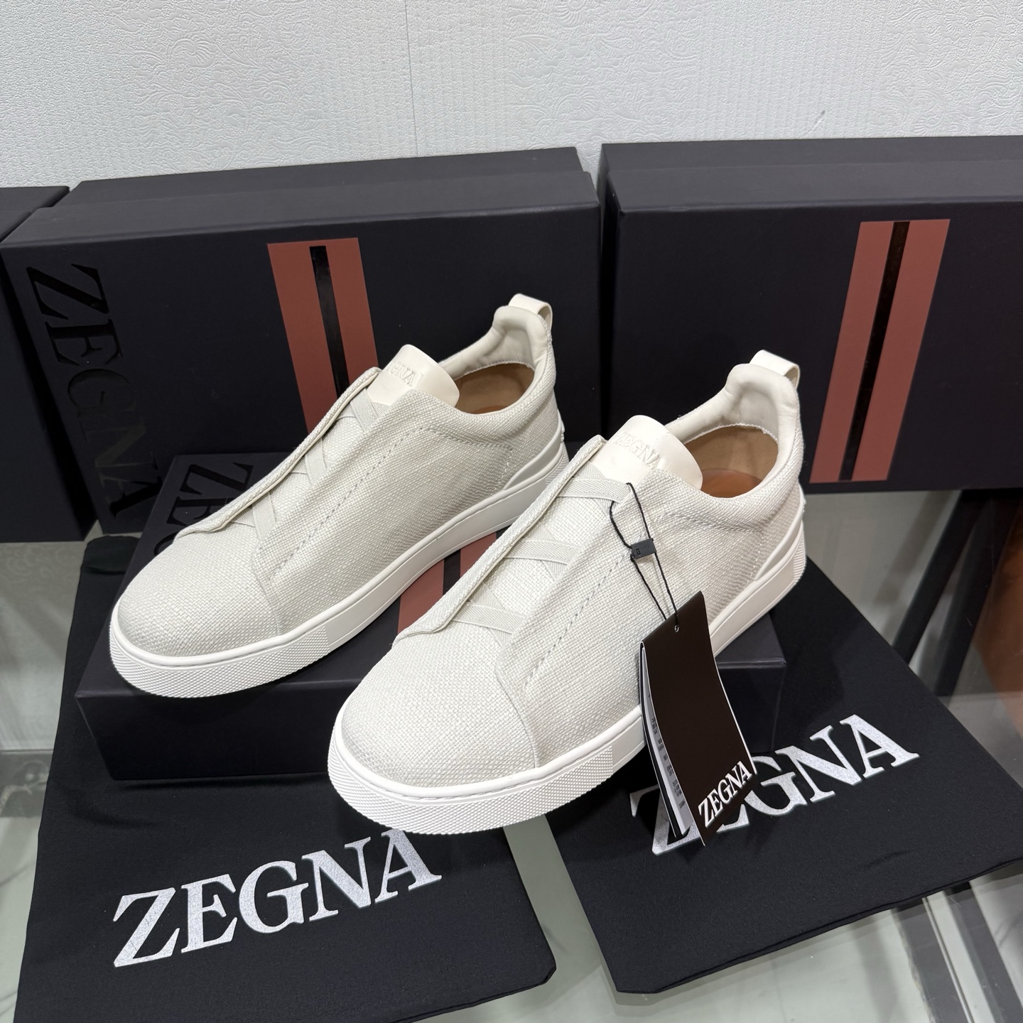 Zegna/杰尼亚 SECONDSKIN Triple Stitch&trade; 休闲运动鞋，帆布系列
这款低帮运动鞋的鞋面光滑柔软。饰以标志性三重交叉松紧细节，致敬品牌精裁夹克的手工缝制工艺。设计轻盈，与白色橡胶鞋底相得益彰，专为快节奏的生活方式打造。这款鞋汲取手套制作灵感，融汇世代工匠经验智慧，选用新西兰顶级小牛皮制作，成就轻盈质地，精致衬里结合非凡韧性。带来独一无二的贴合感。非常轻盈的橡胶外底上点缀双条纹 Logo 运动细节，以超轻结构重新诠释标志性鞋款。领口部位鹿皮面料反车做法，无内裡车中底套楦做法。易穿脱套脚交叉松紧带和 3D&ldquo;波纹&rdquo;设计。鞋舌热压品牌名称。
后跟加贴 TPU 双条纹品牌 Logo 饰条，鞋身空胶做法，周圈加车大底缝线。轻盈的高弹力橡胶外底背面和可拆卸脚床饰 Zegna 标识，为这款运动鞋增添现代动感气息。
皮鞋码数:39/40/41/42/43/44/45/46/47 
专柜包装，现货