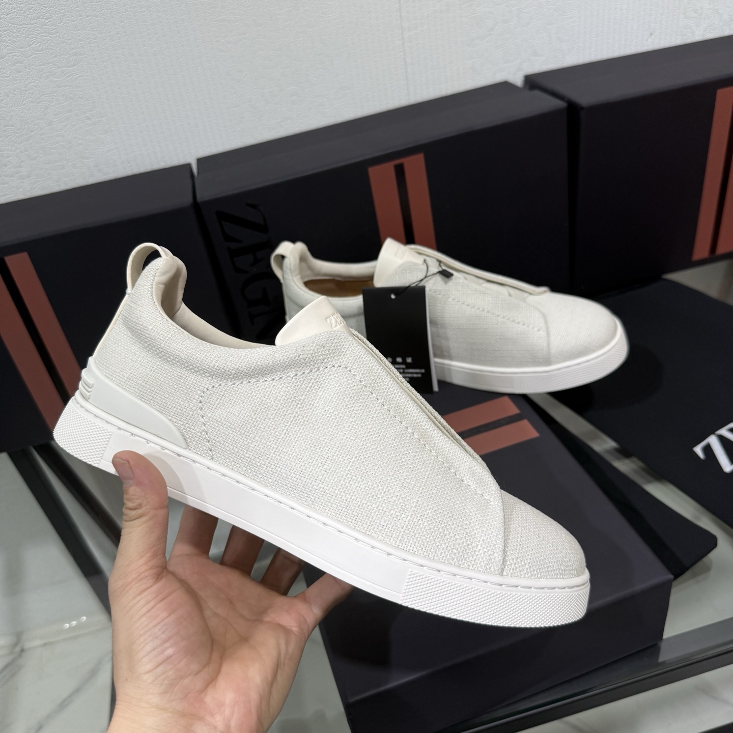 Zegna/杰尼亚 SECONDSKIN Triple Stitch&trade; 休闲运动鞋，帆布系列
这款低帮运动鞋的鞋面光滑柔软。饰以标志性三重交叉松紧细节，致敬品牌精裁夹克的手工缝制工艺。设计轻盈，与白色橡胶鞋底相得益彰，专为快节奏的生活方式打造。这款鞋汲取手套制作灵感，融汇世代工匠经验智慧，选用新西兰顶级小牛皮制作，成就轻盈质地，精致衬里结合非凡韧性。带来独一无二的贴合感。非常轻盈的橡胶外底上点缀双条纹 Logo 运动细节，以超轻结构重新诠释标志性鞋款。领口部位鹿皮面料反车做法，无内裡车中底套楦做法。易穿脱套脚交叉松紧带和 3D&ldquo;波纹&rdquo;设计。鞋舌热压品牌名称。
后跟加贴 TPU 双条纹品牌 Logo 饰条，鞋身空胶做法，周圈加车大底缝线。轻盈的高弹力橡胶外底背面和可拆卸脚床饰 Zegna 标识，为这款运动鞋增添现代动感气息。
皮鞋码数:39/40/41/42/43/44/45/46/47 
专柜包装，现货