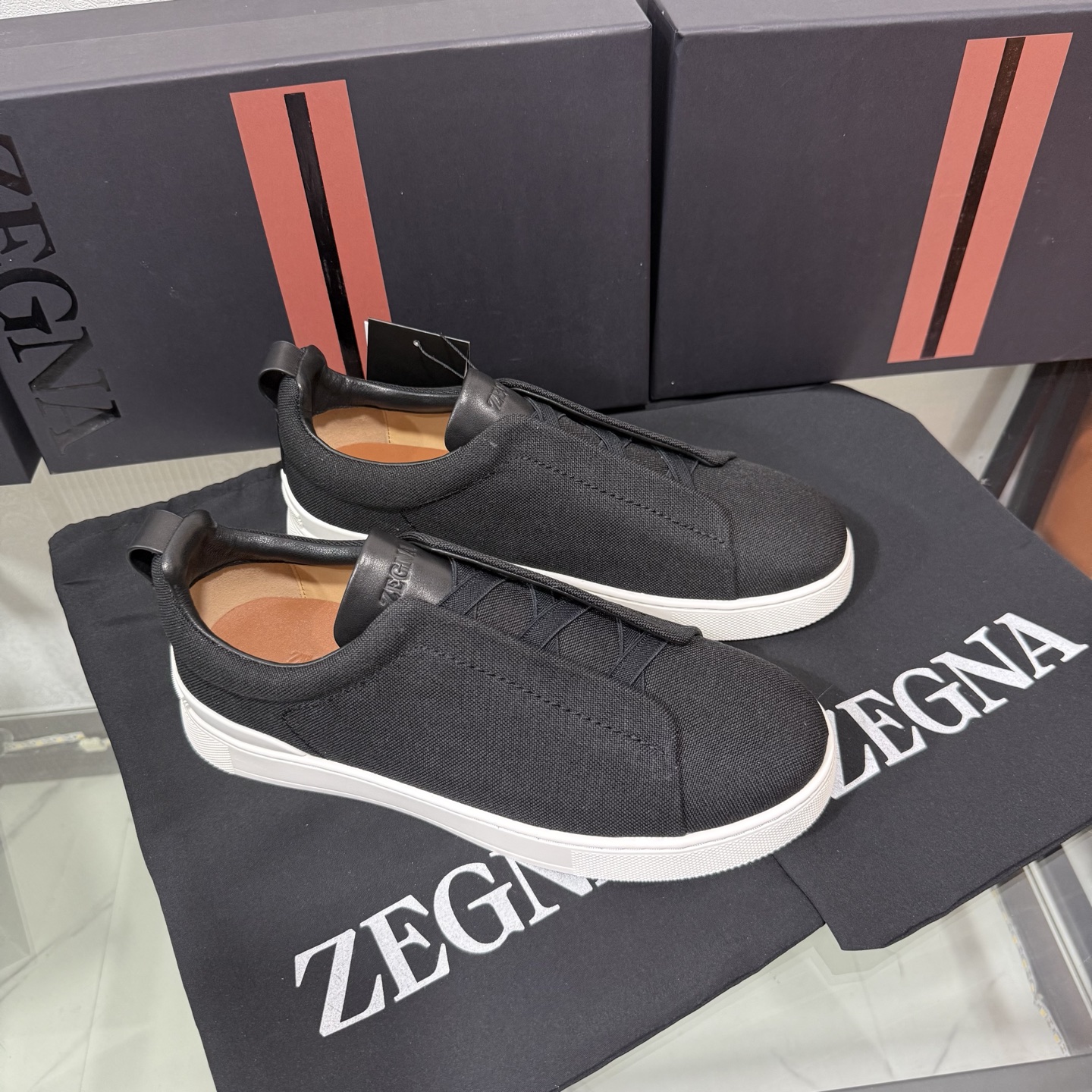 Zegna/杰尼亚 SECONDSKIN Triple Stitch&trade; 休闲运动鞋，帆布系列
这款低帮运动鞋的鞋面光滑柔软。饰以标志性三重交叉松紧细节，致敬品牌精裁夹克的手工缝制工艺。设计轻盈，与白色橡胶鞋底相得益彰，专为快节奏的生活方式打造。这款鞋汲取手套制作灵感，融汇世代工匠经验智慧，选用新西兰顶级小牛皮制作，成就轻盈质地，精致衬里结合非凡韧性。带来独一无二的贴合感。非常轻盈的橡胶外底上点缀双条纹 Logo 运动细节，以超轻结构重新诠释标志性鞋款。领口部位鹿皮面料反车做法，无内裡车中底套楦做法。易穿脱套脚交叉松紧带和 3D&ldquo;波纹&rdquo;设计。鞋舌热压品牌名称。
后跟加贴 TPU 双条纹品牌 Logo 饰条，鞋身空胶做法，周圈加车大底缝线。轻盈的高弹力橡胶外底背面和可拆卸脚床饰 Zegna 标识，为这款运动鞋增添现代动感气息。
皮鞋码数:39/40/41/42/43/44/45/46/47 ，48
专柜包装，现货