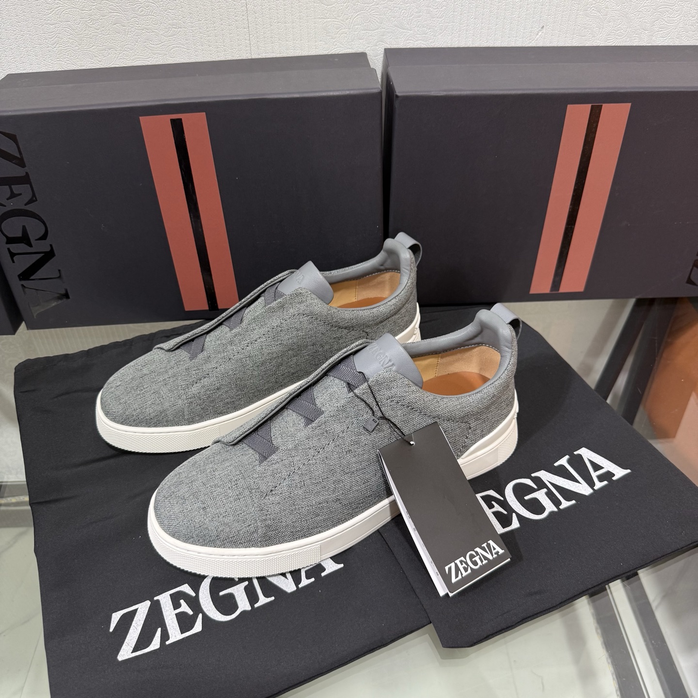 Zegna/杰尼亚 SECONDSKIN Triple Stitch&trade; 休闲运动鞋，帆布系列
这款低帮运动鞋的鞋面光滑柔软。饰以标志性三重交叉松紧细节，致敬品牌精裁夹克的手工缝制工艺。设计轻盈，与白色橡胶鞋底相得益彰，专为快节奏的生活方式打造。这款鞋汲取手套制作灵感，融汇世代工匠经验智慧，选用新西兰顶级小牛皮制作，成就轻盈质地，精致衬里结合非凡韧性。带来独一无二的贴合感。非常轻盈的橡胶外底上点缀双条纹 Logo 运动细节，以超轻结构重新诠释标志性鞋款。领口部位鹿皮面料反车做法，无内裡车中底套楦做法。易穿脱套脚交叉松紧带和 3D&ldquo;波纹&rdquo;设计。鞋舌热压品牌名称。
后跟加贴 TPU 双条纹品牌 Logo 饰条，鞋身空胶做法，周圈加车大底缝线。轻盈的高弹力橡胶外底背面和可拆卸脚床饰 Zegna 标识，为这款运动鞋增添现代动感气息。
皮鞋码数:39/40/41/42/43/44/45/46/47 
专柜包装，现货