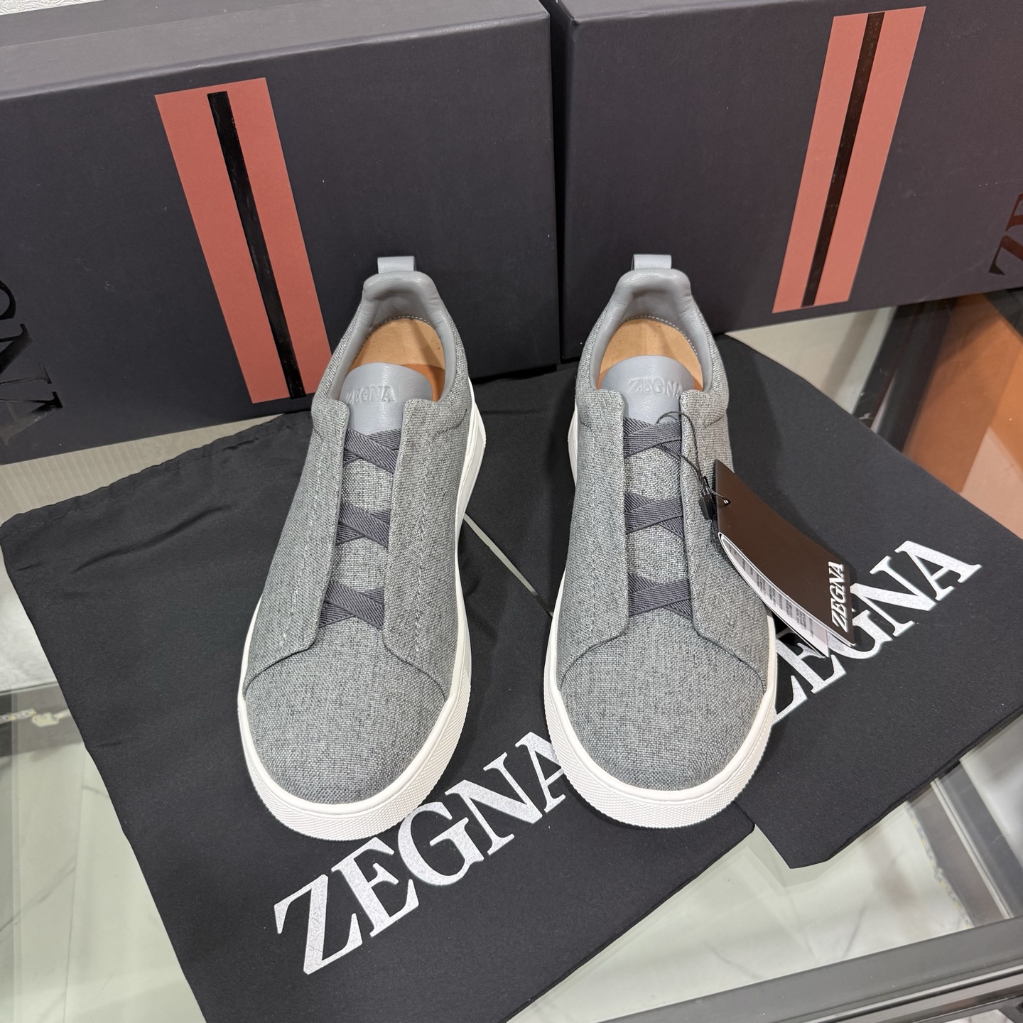 Zegna/杰尼亚 SECONDSKIN Triple Stitch&trade; 休闲运动鞋，帆布系列
这款低帮运动鞋的鞋面光滑柔软。饰以标志性三重交叉松紧细节，致敬品牌精裁夹克的手工缝制工艺。设计轻盈，与白色橡胶鞋底相得益彰，专为快节奏的生活方式打造。这款鞋汲取手套制作灵感，融汇世代工匠经验智慧，选用新西兰顶级小牛皮制作，成就轻盈质地，精致衬里结合非凡韧性。带来独一无二的贴合感。非常轻盈的橡胶外底上点缀双条纹 Logo 运动细节，以超轻结构重新诠释标志性鞋款。领口部位鹿皮面料反车做法，无内裡车中底套楦做法。易穿脱套脚交叉松紧带和 3D&ldquo;波纹&rdquo;设计。鞋舌热压品牌名称。
后跟加贴 TPU 双条纹品牌 Logo 饰条，鞋身空胶做法，周圈加车大底缝线。轻盈的高弹力橡胶外底背面和可拆卸脚床饰 Zegna 标识，为这款运动鞋增添现代动感气息。
皮鞋码数:39/40/41/42/43/44/45/46/47 
专柜包装，现货