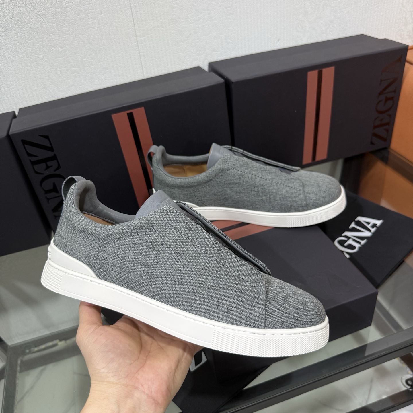 Zegna/杰尼亚 SECONDSKIN Triple Stitch&trade; 休闲运动鞋，帆布系列
这款低帮运动鞋的鞋面光滑柔软。饰以标志性三重交叉松紧细节，致敬品牌精裁夹克的手工缝制工艺。设计轻盈，与白色橡胶鞋底相得益彰，专为快节奏的生活方式打造。这款鞋汲取手套制作灵感，融汇世代工匠经验智慧，选用新西兰顶级小牛皮制作，成就轻盈质地，精致衬里结合非凡韧性。带来独一无二的贴合感。非常轻盈的橡胶外底上点缀双条纹 Logo 运动细节，以超轻结构重新诠释标志性鞋款。领口部位鹿皮面料反车做法，无内裡车中底套楦做法。易穿脱套脚交叉松紧带和 3D&ldquo;波纹&rdquo;设计。鞋舌热压品牌名称。
后跟加贴 TPU 双条纹品牌 Logo 饰条，鞋身空胶做法，周圈加车大底缝线。轻盈的高弹力橡胶外底背面和可拆卸脚床饰 Zegna 标识，为这款运动鞋增添现代动感气息。
皮鞋码数:39/40/41/42/43/44/45/46/47 
专柜包装，现货