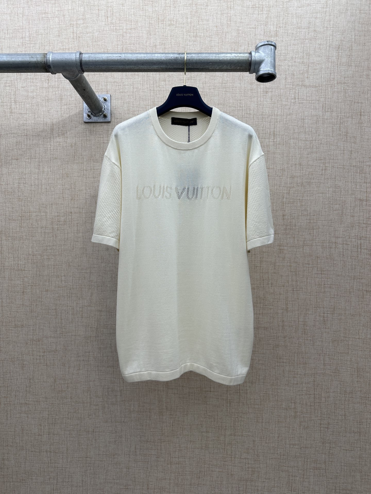LV/路易威登 网眼镂空短袖针织衫 2026 FW 当季新款系列LV标识胸前以镂空提花工艺呈现「LOUIS VUITTON」品牌字母，在光线下可透出内层，拉满的高级视觉效果。 面料主料为：100%棉，整体采用网眼镂空（Pointelle）…