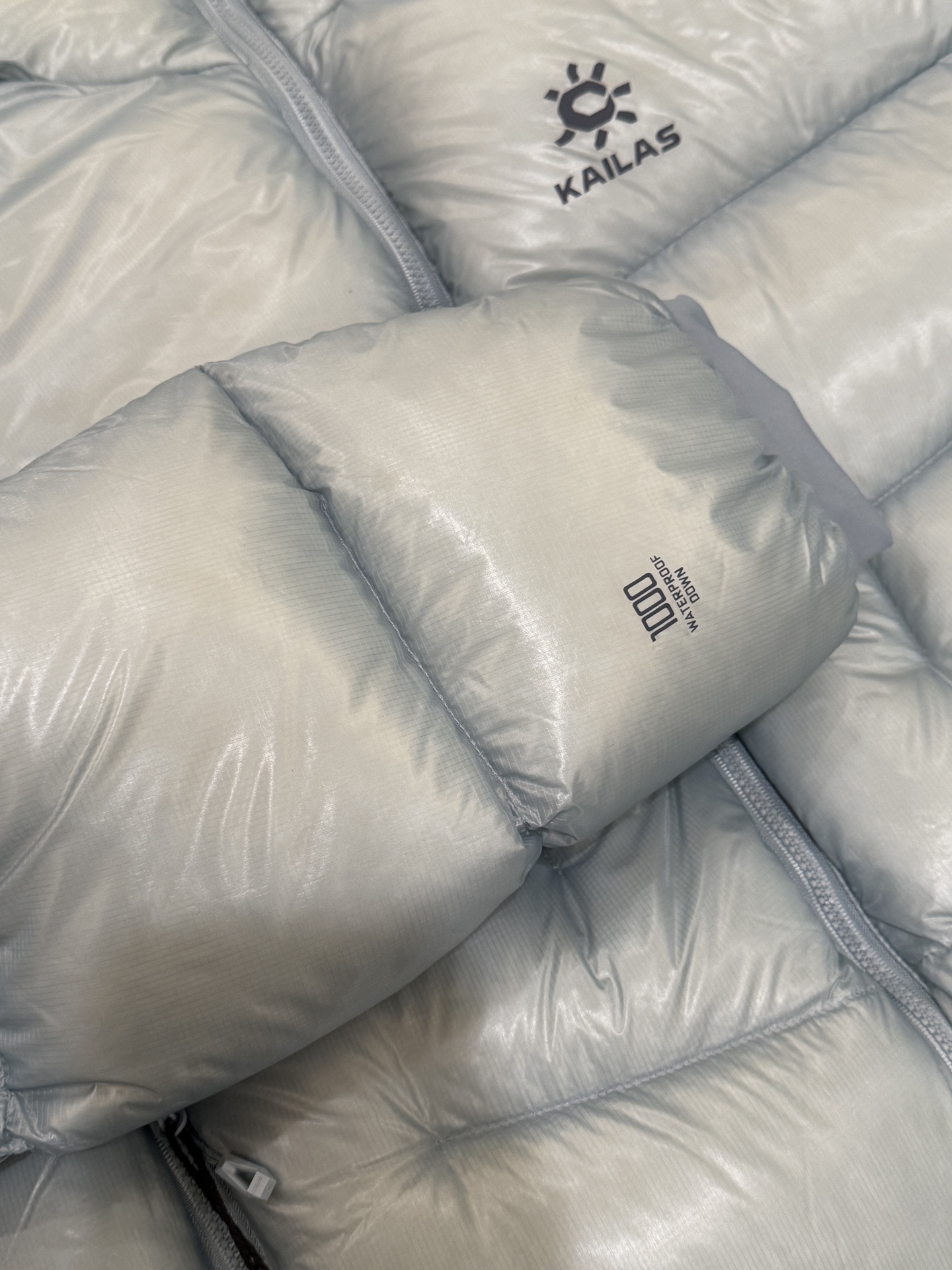 私域版高货!KAILAS 凯乐石 5000GT 颜色 天池蓝 千蓬元帅户外运动登山徒步轻量透气拒水1000蓬羽绒服 超级轻薄半透面料,绒朵透光可见,所以这款填充绒必须足够好,否则没法看! 肉眼可见的超级蓬松,这款因为填充的绒朵好,才能呈现出鼓鼓囊囊的效果,超轻超蓬! 填充国标拒水90白鹅绒(清水绒),支持检测!区别于市面假90绒. 面料为涤纶暗格,市面无同款面料,定制定染色后再做防水;为还原原版质感与手感,打样无数次才最终满意.里布工艺同样复杂,生产周期漫长. 所有五金辅料均为定制定染色:整衣采用三种不同拉链头,内里口袋配特殊色拉链,帽子及下摆抽绳、帽子气眼,均攻克极高工艺难度,完美呈现. 尺码建议:版型偏大,原版数据一刀未改,且可通过下摆内侧抽绳调整至合适效果. 产品配色:松翠绿、玉雪粉、栗色棕、玄铁黑、天池蓝乌木灰