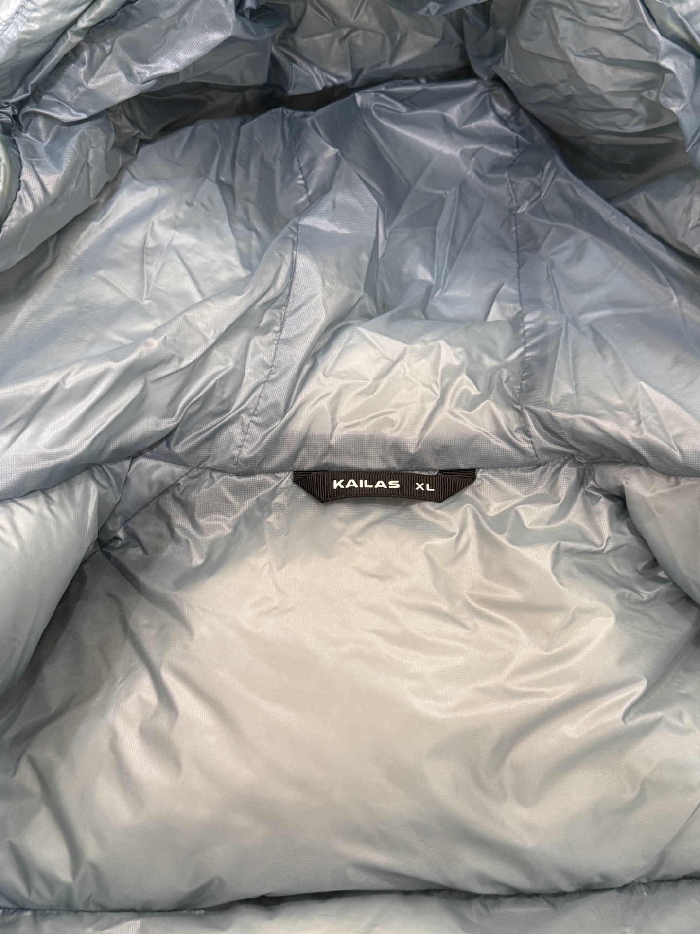 私域版高货!KAILAS 凯乐石 5000GT 颜色 天池蓝 千蓬元帅户外运动登山徒步轻量透气拒水1000蓬羽绒服 超级轻薄半透面料,绒朵透光可见,所以这款填充绒必须足够好,否则没法看! 肉眼可见的超级蓬松,这款因为填充的绒朵好,才能呈现出鼓鼓囊囊的效果,超轻超蓬! 填充国标拒水90白鹅绒(清水绒),支持检测!区别于市面假90绒. 面料为涤纶暗格,市面无同款面料,定制定染色后再做防水;为还原原版质感与手感,打样无数次才最终满意.里布工艺同样复杂,生产周期漫长. 所有五金辅料均为定制定染色:整衣采用三种不同拉链头,内里口袋配特殊色拉链,帽子及下摆抽绳、帽子气眼,均攻克极高工艺难度,完美呈现. 尺码建议:版型偏大,原版数据一刀未改,且可通过下摆内侧抽绳调整至合适效果. 产品配色:松翠绿、玉雪粉、栗色棕、玄铁黑、天池蓝乌木灰