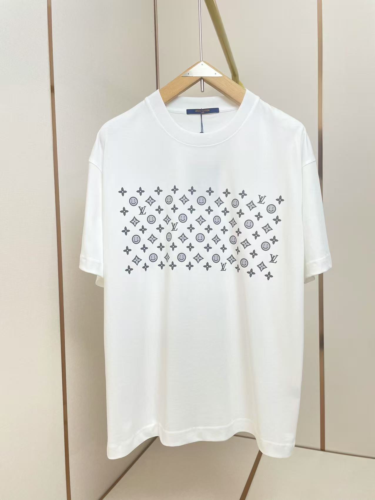 NO:428223,LV New CPFM Smiling T-shirt The front of the T-shirt is printed with dark-colored repeating patterns, including abstract smiley symbols, four-leaf clover patterns and modular arrangement of the brand letter 'T', forming a modern geometric artistic effect. The smiley elements add interestingness to daily outfits and are a versatile and fashionable basic item. Shoulder shoulder pressure strips 280 grams pure cotton fabric is comfortable and breathable, black and white, same style as men and women. Size S-XXL.,,louis vuitton,tees, t-shirt,alexander wang19860909LV 新款CPFM笑脸T恤 T恤正面印有深色系重复图案组合包含抽象笑脸符号、四叶草花纹以及品牌字母'T'的模块化排列,形成现代几何艺术效果 笑脸元素为日常穿搭增添趣味性,属于百搭型时尚基础款单品.肩部通肩压条 280克纯棉面料舒适透气 黑白双色 男女同款 码数S-XXL .,,louis vuitton,tees，t-shirt,alexander wang,Men's clothing