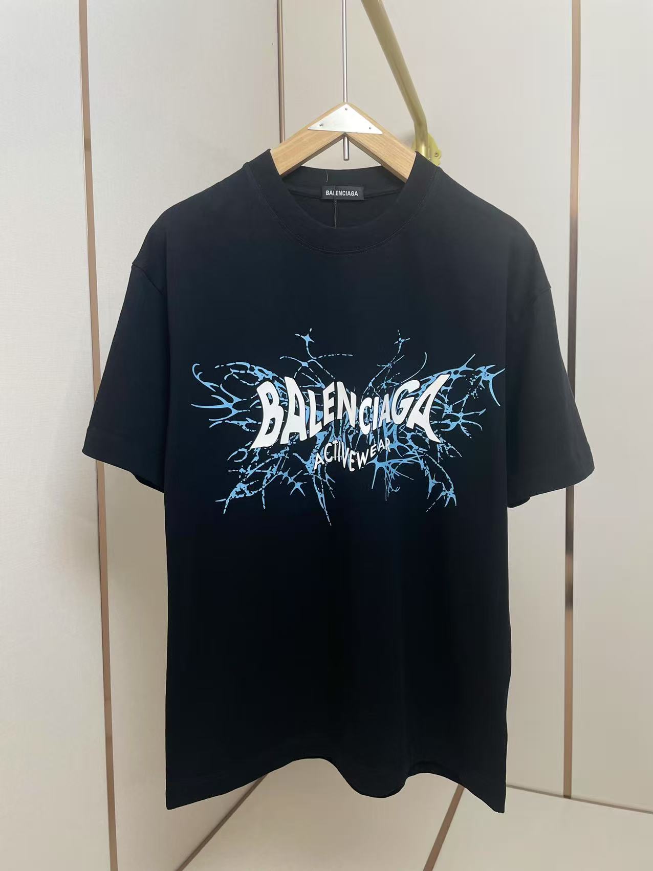 NO:428191,Balenciaga Activewear series short-sleeved T-shirts adopt the brand's iconic minimalist silhouette design. The front of the T-shirt is printed with 'BALENCIAGA ACTIVEWEAR' in black font, and the letter edges have blue crack ink dyeing special effects, injecting street art into the basic style. The contrasting color design of blue and black ink splashing font and black and white background continues the brand's main deconstructive aesthetic language in recent years. Shoulder shoulder pressure strips 280 grams pure cotton fabric is comfortable and breathable, black and white, same as men and women. S-XXL,,balenciaga,balenciaga,T-shirt,tees,t-shirt,alexander wang19860909巴黎世家 Activewear系列短袖T恤,采用品牌标志性的极简廓形设计.T恤正面以黑色字体印刷'BALENCIAGA ACTIVEWEAR'字样,字母边缘带有蓝色裂纹墨染特效,为基本款注入街头艺术感.蓝黑泼墨字体与黑色白色底色的撞色设计,延续了品牌近年主打的解构美学语言.肩部通肩压条 280克纯棉面料舒适透气 黑白双色 男女同款 码数S-XXL,,balenciaga,balenciaga,T-shirt,tees，t-shirt,alexander wang,Men's clothing