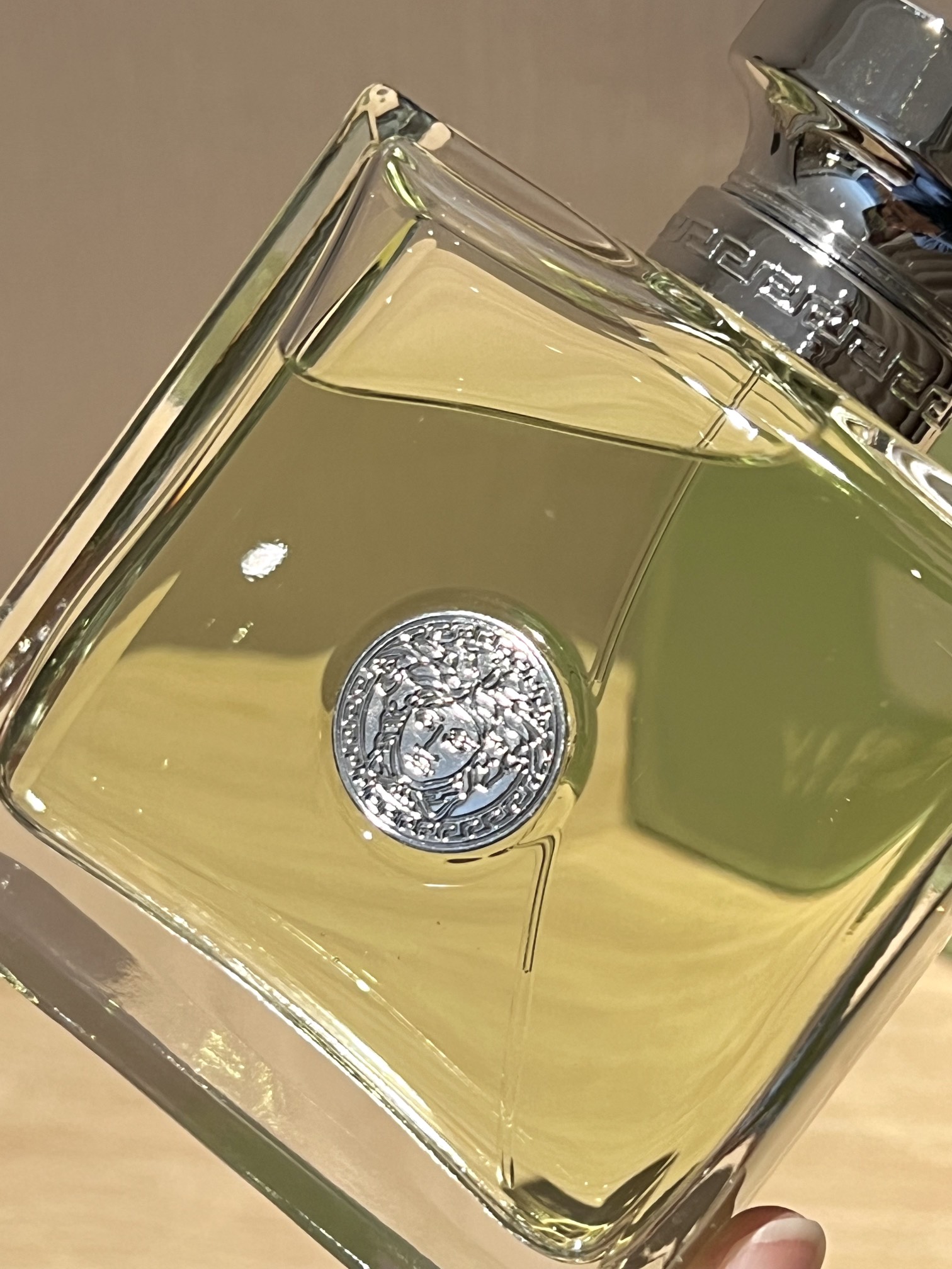 A polished silver-tone Versace logo is centered on the bottle - Comprehensive