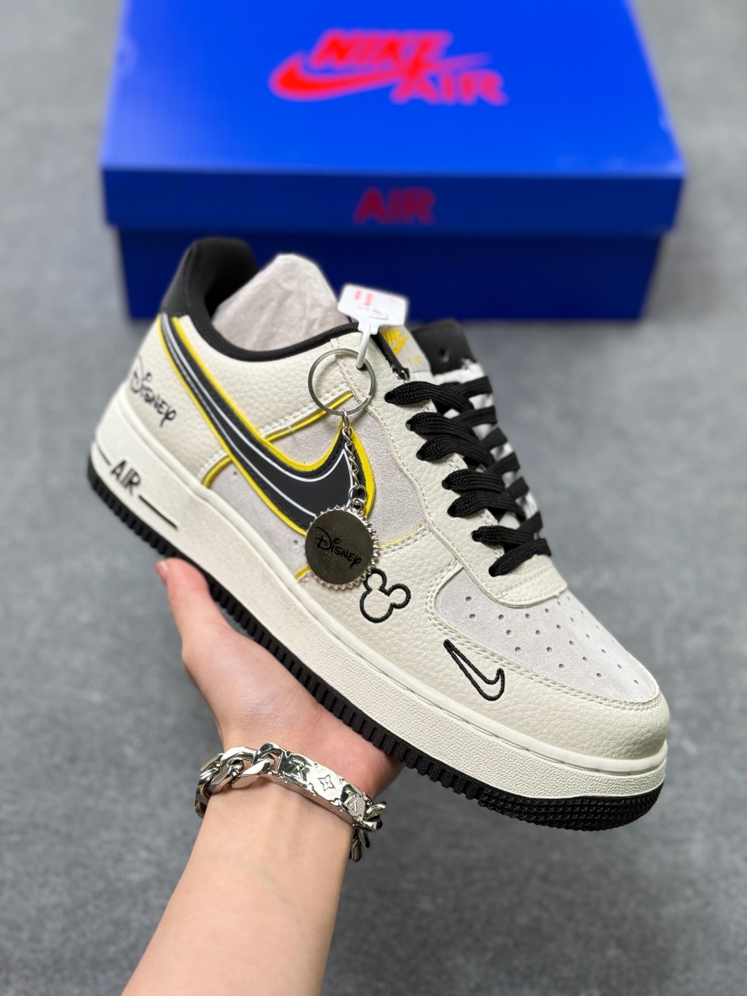 💰220
童趣奢潮碰撞！AF1 Low x Disney 联名款唤醒童年DNA
 当Nike Air Force 1 Low的经典街头骨架遇上迪士尼的童话基因，这双SY1388-021联名款直接把「潮玩童趣」焊在了鞋面上！
 鞋身以奶白荔枝纹皮革搭配浅灰磨砂皮打造基底，黑黄撞色的Swoosh线条利落又俏皮，黄色包边如漫画描边般勾勒出灵动质感。鞋头的米奇轮廓简笔画、鞋侧的Disney手写体标识，将迪士尼的经典元素以手绘风呈现，细节处满是童真巧思；黑白撞色鞋带搭配经典AF1中底的「AIR」标识，保留了空军一号的街头底蕴，让童趣与潮流实现完美平衡。
 作为AF1与迪士尼的跨界联名，这双鞋既延续了Air Force 1 Low的百搭属性，又凭借迪士尼的IP加持成为吸睛利器。不管是日常出街打造甜酷造型，还是作为迪士尼粉丝的收藏款，这双AF1 Low x Disney联名款都能让你在潮流圈玩转出独特的童趣风格，属于大人的童话潮鞋，入手即解锁双倍快乐！
size：36-45半 X3