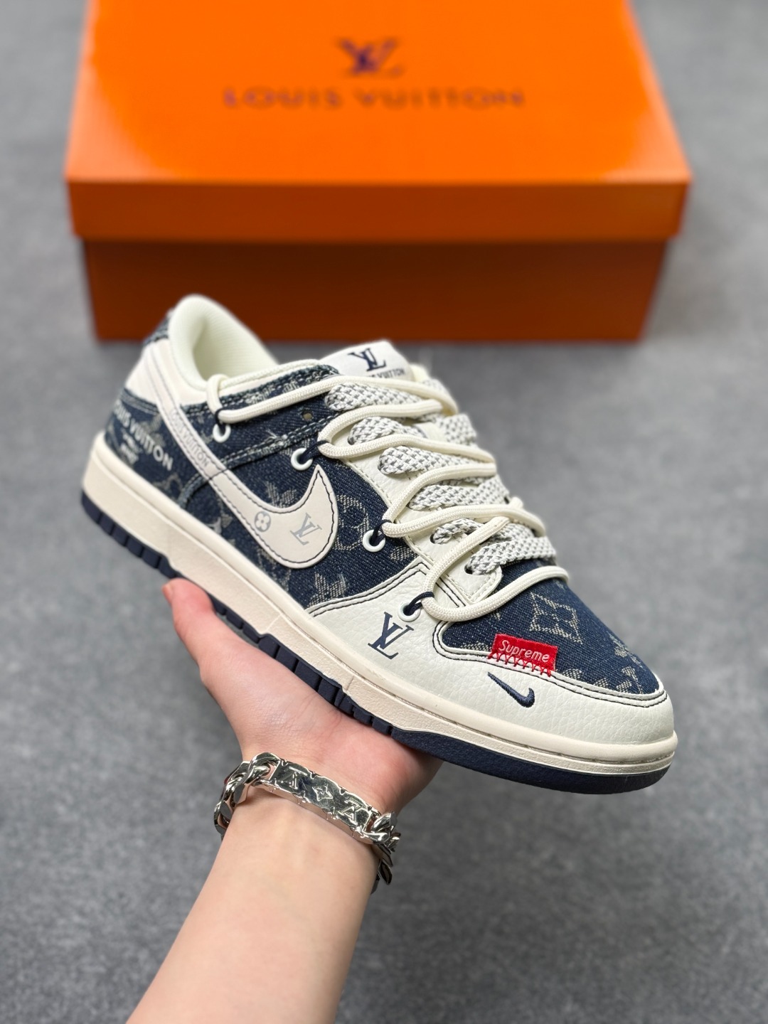 单宁老花炸场,Dunk Low 奢潮联名款诠释街头顶配 Nike Dunk Low YX5066-397 款直接把街头与奢华的融合玩到极致,经典滑板鞋型遇上丹宁老花布料的拼接,藏青丹宁的粗粝质感碰撞米白皮革的细腻,鞋侧 Swoosh 嵌着 LV 老花暗纹,鞋头的 Supreme 红标与鞋身“LOUIS VUITTON”字母标识相互呼应,每一处细节都透着奢潮联名的独特腔调.保留 Dunk Low 标志性的低帮轮廓与橡胶大底的扎实脚感,既延续了滑板鞋的街头基因,又注入奢牌的精致美学,是潮人鞋柜里的收藏级狠货.上脚这双鞋,轻松解锁单宁与老花的高阶混搭,走在街头,就是移动的潮流风向标. 半 x3
