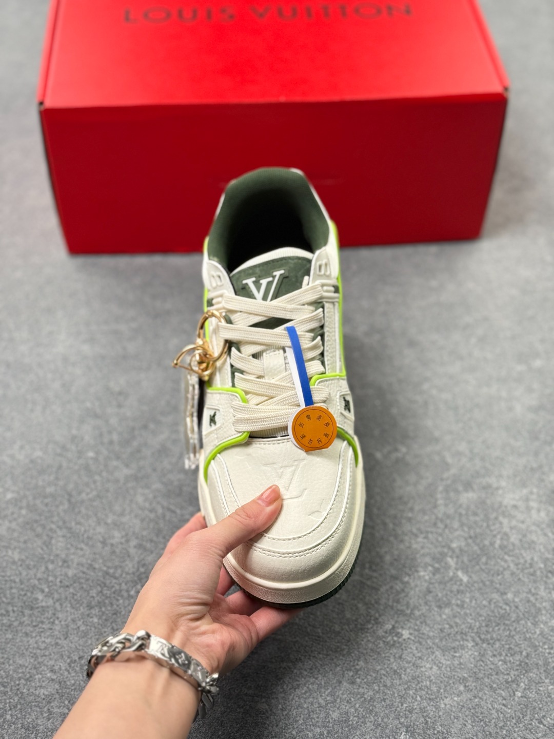 LV TRAINER白灰+荧光绿(中国红限定礼盒版本-钥匙扣丢失扣20元) 26年限定中国红礼盒及全套包装说明书防尘布袋物件,完美楦型,独家开模定制! trainer这个系列是路易威登融合街头潮流与高级时装的标志性之作.在材料选用上,鞋面采用Monogram印花与Monogram压纹粒面牛皮革的搭配,呈现出独特的复古韵味.荔枝纹粒面头层牛革鞋面,触感细腻且富有韧性,自带自然的皮革纹理,彰显高级质感,为鞋子增添了丰富的层次感.鞋垫采用原版超软乳胶材质,新鞋零磨合不磨脚,软乎乎的皮质包裹感超棒,鞋底则采用橡胶材质,刻有经典的Monogram花卉纹路,不仅防滑,还带走缓震效果还极具设计感.做工方面,TRAINER系列板鞋展现了精湛的工艺水准.鞋头采用圆润设计,原版空胶工艺搭配包边工艺,不仅美观,还能有效防踢蹭.鞋舌、侧面和后部饰有LV字母,侧面还有Vuitton标识,均做工精细,彰显品牌身份.鞋身走线工整均匀,看不到任何多余的线头,皮革的拼接处也处理得极为细腻,体现了我们对细节的极致追求.百搭属性直接封神!配牛仔裤是复古街头风,搭西装裤秒变松弛通勤感,甚至配半身裙都甜妹感拉满,堪称"衣柜万能钥匙".这双集颜值、质感、实穿性于一体的奢牌板鞋! 货号:2A8DM18VL IZE:36 37 38 39 40 41 42 43 44 45(不带半)x45