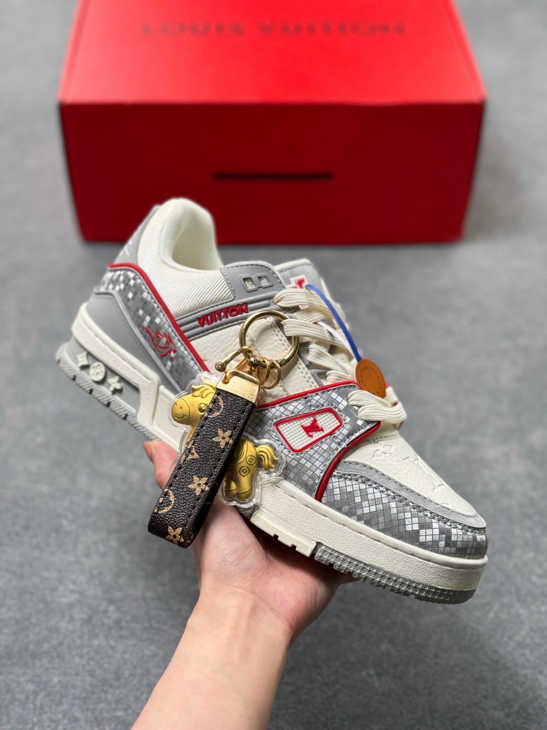 LV TRAINER浅灰格纹(中国红限定礼盒版本-钥匙扣丢失扣20元) 26年限定中国红礼盒及全套包装说明书防尘布袋物件,完美楦型,独家开模定制! trainer这个系列是路易威登融合街头潮流与高级时装的标志性之作.在材料选用上,鞋面采用Monogram印花与Monogram压纹粒面牛皮革的搭配,呈现出独特的复古韵味.荔枝纹粒面头层牛革鞋面,触感细腻且富有韧性,自带自然的皮革纹理,彰显高级质感,为鞋子增添了丰富的层次感.鞋垫采用原版超软乳胶材质,新鞋零磨合不磨脚,软乎乎的皮质包裹感超棒,鞋底则采用橡胶材质,刻有经典的Monogram花卉纹路,不仅防滑,还带走缓震效果还极具设计感.做工方面,TRAINER系列板鞋展现了精湛的工艺水准.鞋头采用圆润设计,原版空胶工艺搭配包边工艺,不仅美观,还能有效防踢蹭.鞋舌、侧面和后部饰有LV字母,侧面还有Vuitton标识,均做工精细,彰显品牌身份.鞋身走线工整均匀,看不到任何多余的线头,皮革的拼接处也处理得极为细腻,体现了我们对细节的极致追求.百搭属性直接封神!配牛仔裤是复古街头风,搭西装裤秒变松弛通勤感,甚至配半身裙都甜妹感拉满,堪称"衣柜万能钥匙".这双集颜值、质感、实穿性于一体的奢牌板鞋! 货号:2A8DM25VL IZE:36 37 38 39 40 41 42 43 44 45(不带半)x45