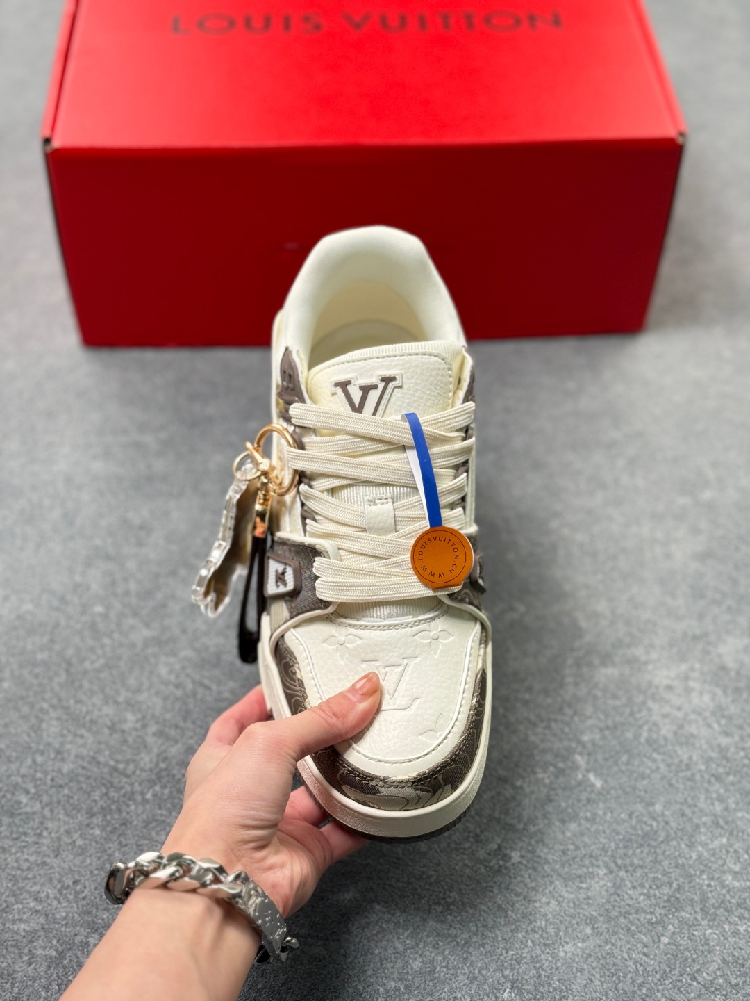 LV TRAINER迷彩马纹(中国红限定礼盒版本-钥匙扣丢失扣20元) 26年限定中国红礼盒及全套包装说明书防尘布袋物件,完美楦型,独家开模定制! trainer这个系列是路易威登融合街头潮流与高级时装的标志性之作.在材料选用上,鞋面采用Monogram印花与Monogram压纹粒面牛皮革的搭配,呈现出独特的复古韵味.荔枝纹粒面头层牛革鞋面,触感细腻且富有韧性,自带自然的皮革纹理,彰显高级质感,为鞋子增添了丰富的层次感.鞋垫采用原版超软乳胶材质,新鞋零磨合不磨脚,软乎乎的皮质包裹感超棒,鞋底则采用橡胶材质,刻有经典的Monogram花卉纹路,不仅防滑,还带走缓震效果还极具设计感.做工方面,TRAINER系列板鞋展现了精湛的工艺水准.鞋头采用圆润设计,原版空胶工艺搭配包边工艺,不仅美观,还能有效防踢蹭.鞋舌、侧面和后部饰有LV字母,侧面还有Vuitton标识,均做工精细,彰显品牌身份.鞋身走线工整均匀,看不到任何多余的线头,皮革的拼接处也处理得极为细腻,体现了我们对细节的极致追求.百搭属性直接封神!配牛仔裤是复古街头风,搭西装裤秒变松弛通勤感,甚至配半身裙都甜妹感拉满,堪称"衣柜万能钥匙".这双集颜值、质感、实穿性于一体的奢牌板鞋! 货号:2A8DM21VL IZE:36 37 38 39 40 41 42 43 44 45(不带半)x45