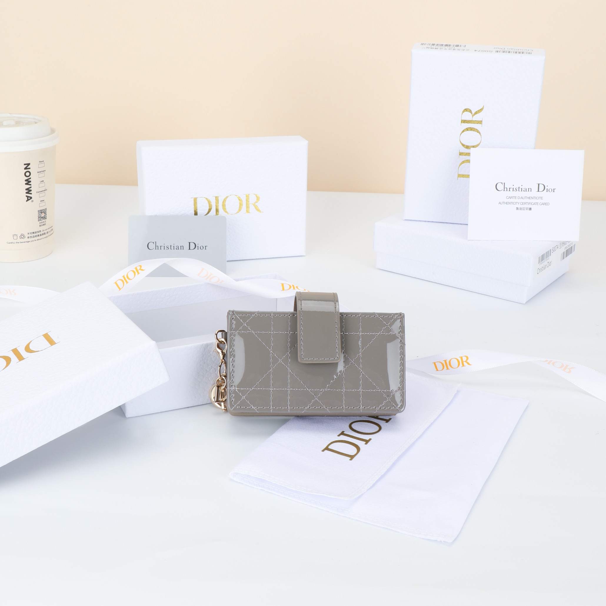 NO:852886,Number: S00740VRB_M51U Size 10.4×7×2cm This Lady Dior Jasmine card holder is decorated with classic cannage topstitching, paying tribute to the exquisite craftsmanship of Dior leather craftsmen. Carefully crafted from marble gray patent cow leather, it is sophisticated and practical and can store a variety of daily necessities. Decorated with gussets, with removable D.I.O.R. charms and strap snap closures, it can be combined with other Lady Dior bags.  Match Dior items to create matching looks.,Dior wallet,dior,wallets,cowhide19860909编号:S00740VRB_M51U 尺寸10.4×7×2cm 这款 Lady Dior Jasmine 卡夹饰有经典的藤格纹缉面线,向 Dior皮 革工匠的精湛工艺致敬.采用云石灰色漆皮牛皮革精心制作,精 实用,可收纳各种日常用品.饰以三角形衬料,搭配可拆卸 D.I.O.R.吊饰和饰带按扣开合,可与其他 Lady Dior单品搭配,打 造配套造型.,Dior钱包,dior,wallets,cowhide,欧美剧