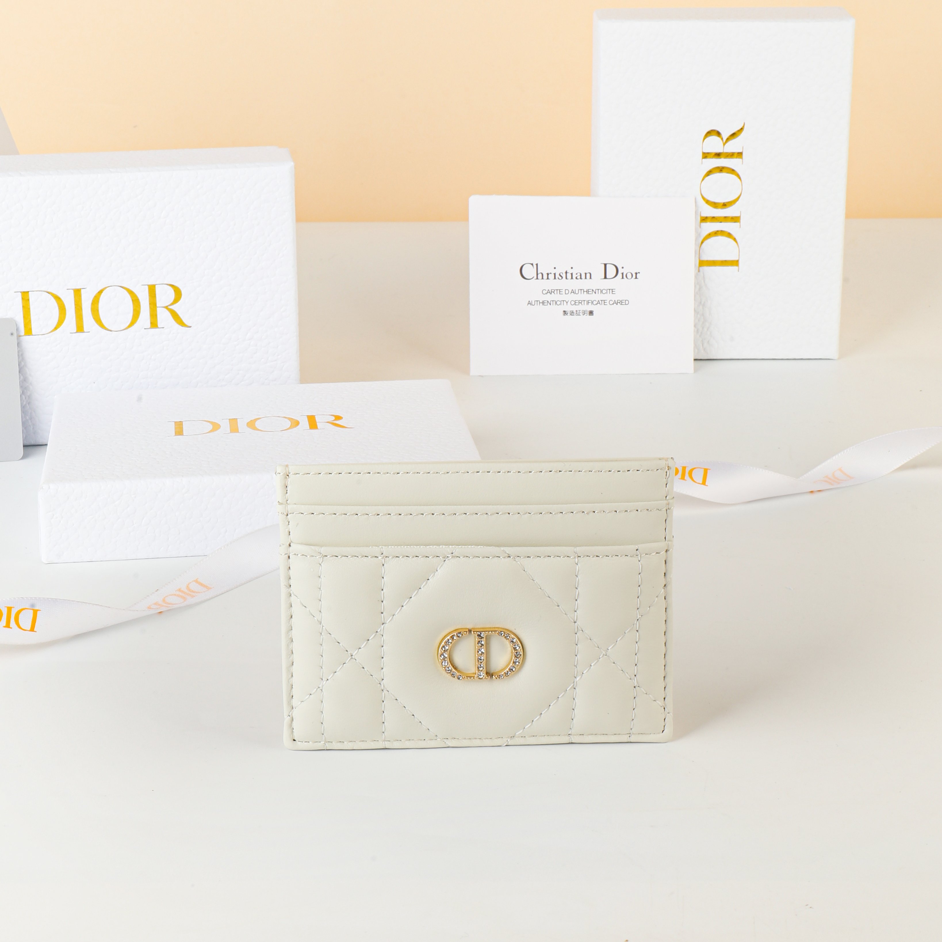 NO:853098,No. S4205UHNN_M900_TU Size 10.5×8×0.5cm This Dior Caro Freesia card holder is a new product in the 2025 autumn and winter ready-to-wear series. It is an elegant and practical accessory. It is carefully made of milky white sheep leather with oversized cannage pattern topstitching. The front is decorated with a gold-finished metal CD logo paved with exquisite white crystals. The elegant style has five card slots, suitable for various occasions and can be combined with other Dior  Caro single product matching., Dior wallet, dior, wallets, sheepskin19860909编号S4205UHNN_M900_TU 尺寸10.5×8×0.5cm 这款 Dior Caro Freesia卡夹是二零二五秋冬成衣系列新品,是一款优雅实用的配饰.采用奶白色羊皮革精心制作,搭配超大藤格纹缉 面线,正面饰以密镶以精美白色晶体的金色饰面金属 CD 标志.款式高雅,设有五个卡槽,适合各种场合,可与其他 Dior Caro单品 搭配.,Dior钱包,dior,wallets,sheepskin,欧美剧