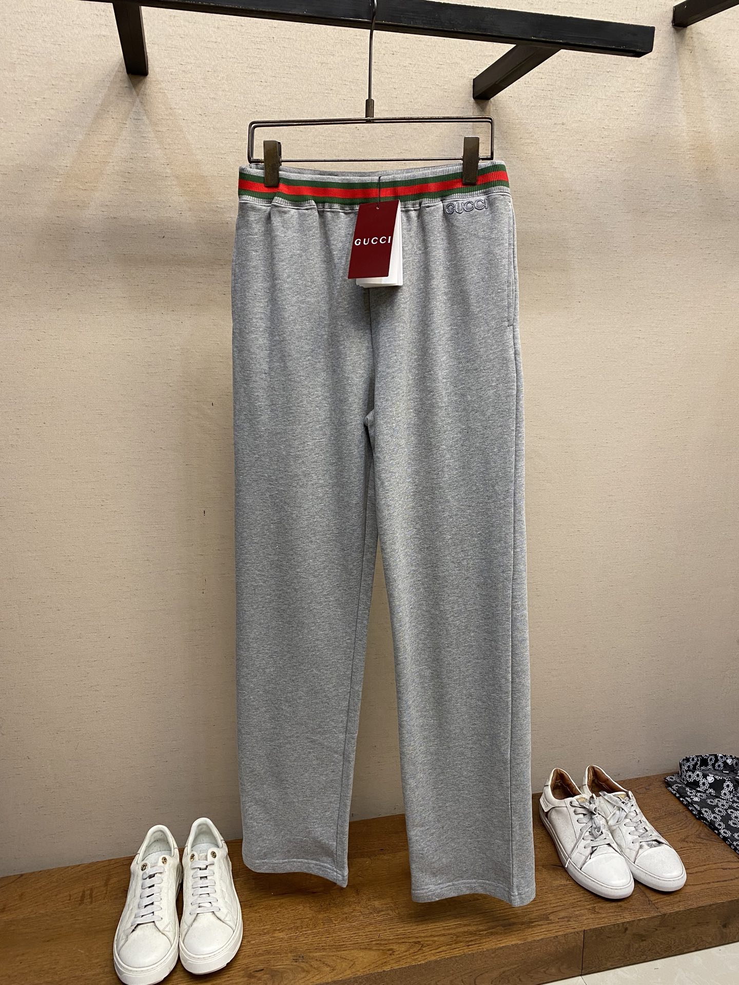 NO:144503,Gucci, GU red and green belt embroidered straight trousers Original, 300 purchase; gray knitted cotton blend fabric, Gc logo patch elastic waist, two side pockets with drawstring, webbing piping, straight casual trousers, full set of auxiliary materials equipped with # gray knitted cotton blend fabric 32S single yarn S fish scale bottom flower gray cotton fabric, 360g. The front is made of flat needle or bead structure; the bottom is made of fish scale terry tissue, which forms a fluffy layer through long or short terry loops. The velvet treatment can enhance the softness when sorted after finishing. Ensure that the surface is flat and delicate, and improve its elasticity and wrinkle resistance. Due to the relatively fine yarn, this sweatshirt fabric feels soft and comfortable to wear. The design of the fish scale bottom also increases the skin-friendliness of the fabric, making the wearing experience better. This fabric has good wear resistance and wrinkle resistance while maintaining softness. #  Red and green webbing piping. Both sides of the front and back show clear red and green stripes, uniform and dense warp and weft yarns; there is no right and reverse, and the process complexity is high, and the warp and weft yarn tension is required to be precisely controlled. The webbing uses special textile to prevent breasts and maintain a soft touch. # Gu logo embroidery patch embroidery process of rice grain needle patch embroidery is a traditional hand-made embroidery technique that combines three-dimensional needle technique and patch inlay, giving the single item a unique texture and artistic sense. The stitches are arranged densely, like rice grain stacking, and form a raised grain feeling through short straight embroidery. It is often used to fill patterns or outline convex and convex texture when touched, similar to relief. # Straight-tune casual trousers  The pants are H-shaped, that is, the trouser legs gradually become wider from the knees, but they will not fully fit the leg curve. This style can well modify the leg lines, cover the body's shortcomings, and at the same time highlight the slenderness of the leg lines. Size XS-L, gucci, hoodie, sweatshirts, alexander wang19860909Gucci、GU红绿带刺绣直筒长裤 原,300购买；灰色针织棉混纺面料、Gc标识贴饰松紧腰头、带抽绳两个侧袋、织带滚边、直筒休闲长裤、全套辅料配备 # 灰色针织棉混纺面料 32S单纱S鱼鳞底花灰棉质面料,360g.正面采用 平针或珠地组织；底面采用鱼鳞毛圈组织,通过长毛圈或短毛圈形成蓬松层,后整理时起绒处理可增强柔软度.确保表面平整细腻,提升其弹性和抗皱性. 由于采用了相对较细的纱线,这种卫衣面料触感柔软,穿着舒适.鱼鳞底的设计也增加了面料的亲肤性,使得穿着体验更佳.使得这种面料在保持柔软的同时,也具备了良好的耐磨和抗皱性能. # 红绿织带滚边 正反两面均呈现清晰的红绿条纹,均匀密实的经纬纱线；无正反之分,工艺复杂度高需精密控制经纬纱线张力.织带两侧采用特殊纺织防止毛边,同时保持柔软触感. # Gu标识刺绣贴饰 米粒针贴布刺绣工艺是一种结合立体针法与贴布镶嵌的传统手工刺绣技艺,赋予单品独特的肌理感和艺术性.针迹密集排列,形似米粒堆叠,通过短直线绣形成凸起颗粒感,常用于填充图案或勾勒轮廓.每针独立且紧密排列,触摸时有细微的凹凸质感,类似浮雕. # 直筒休闲长裤的版型 裤子呈现出H型,即裤管从膝盖处开始逐渐变宽,但不会完全贴合腿部曲线.这种版型能够很好地修饰腿部线条,遮盖身材的不足,同时又能够凸显出腿部线条的修长. 尺码XS-L,,gucci,hoodie,sweatshirts,alexander wang,Men's clothing