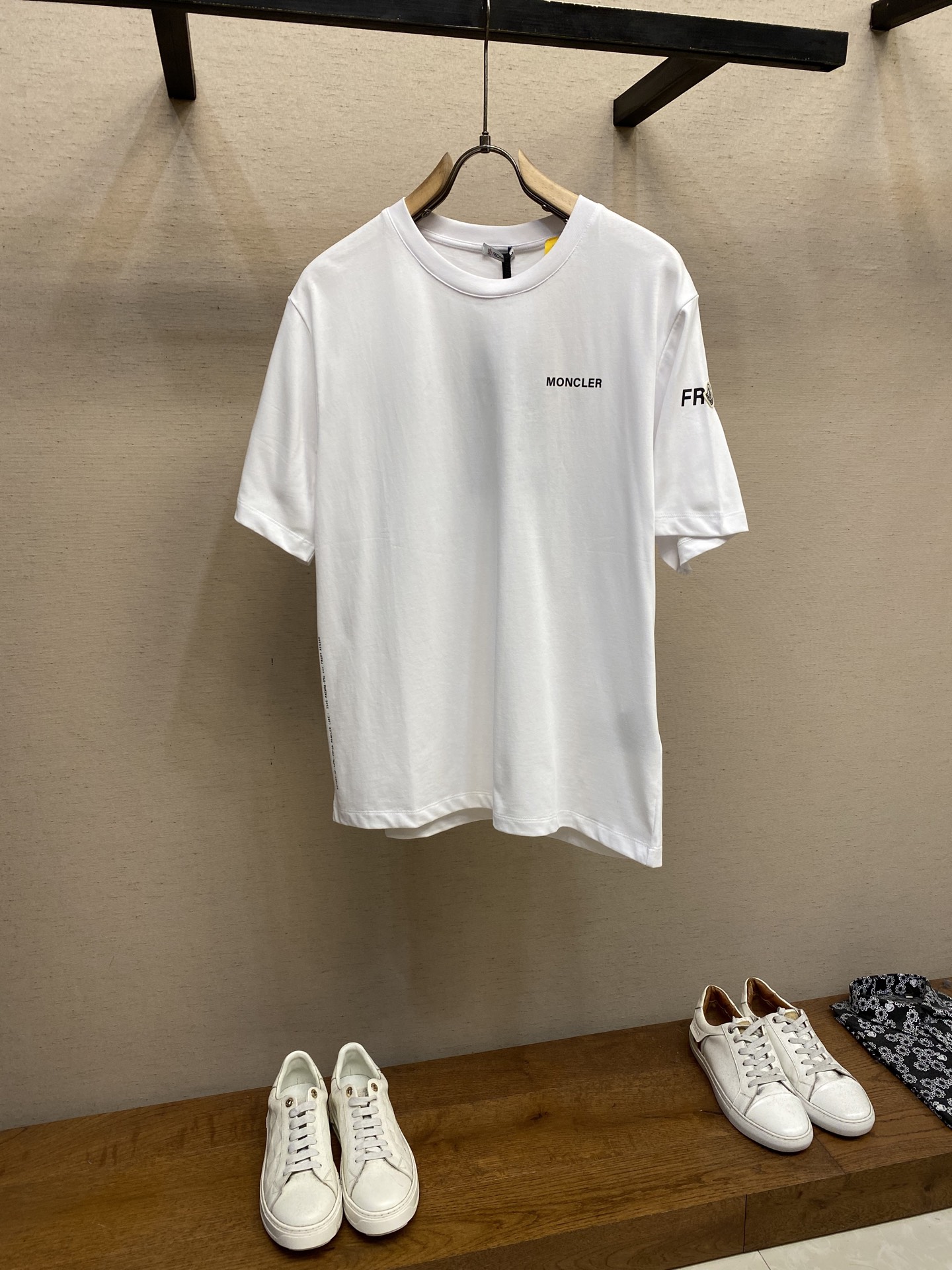 NO:461114,Moncler and Hiro Fujiwara jointly made short-sleeved T-shirt fabric selection. The fabric is made of double-strand cotton plain-woven fabric. The warp and weft yarns are interwoven in one way up and down to form a uniform square texture with a tight but thin structure. The cotton fiber has natural breathability and skin-friendliness. Combined with the pore structure of the plain-weave weave, it is suitable for daily sweating needs and has a good sense of wear. There are many interwoven points, which strengthens tear resistance and can still maintain the shape after multiple washings. Process 1 The fabric is presented with 4 high-saturation patterns through glue printing, and the scraper pressure is uniform. Scratch printing is used to ensure that the glue is fully penetrated and covered. After high-temperature curing, the pigment and cotton fibers are firmly combined. The ink-absorbing and penetration characteristics of the cotton fibers make the pattern not easily fall off due to friction. Process 2  By actively intervening in the shrinking potential of cotton fibers, the fabric has achieved a leap from volatile to stable, improving dimensional stability, and not easily deforming or wrinkling. Size S-XL, T-shirt,tees, t-shirt,alexander wang19860909Moncler、藤原浩联名短袖T恤 面料选择 采用双股棉平纹面料打造而成.经纬纱线以一上一下的方式交织而成,形成均匀的方格状纹理,结构紧密但轻薄.棉纤维具有天然的透气性和亲肤性,结合平纹织法的孔隙结构,适合日常排汗需求的同时兼具良好的穿着舒适感.纱线交织点多,强化抗撕裂能力,多次洗涤仍能保持形态. 工艺1 通过胶浆印花在面料上呈现4处高饱和度图案,刮刀压力均匀,分3次刮印确保胶浆充分渗透并覆盖.再通过高温固化后,颜料与棉纤维结合牢固,棉纤维的吸墨渗透特性使图案不易因摩擦导致脱落. 工艺2 通过主动干预棉纤维收缩潜能,实现了面料从易变到稳定的跨越,提升了尺寸稳定性,同时不易变形,褶皱. 尺码S-XL,,T-shirt,tees，t-shirt,alexander wang,Men's clothing