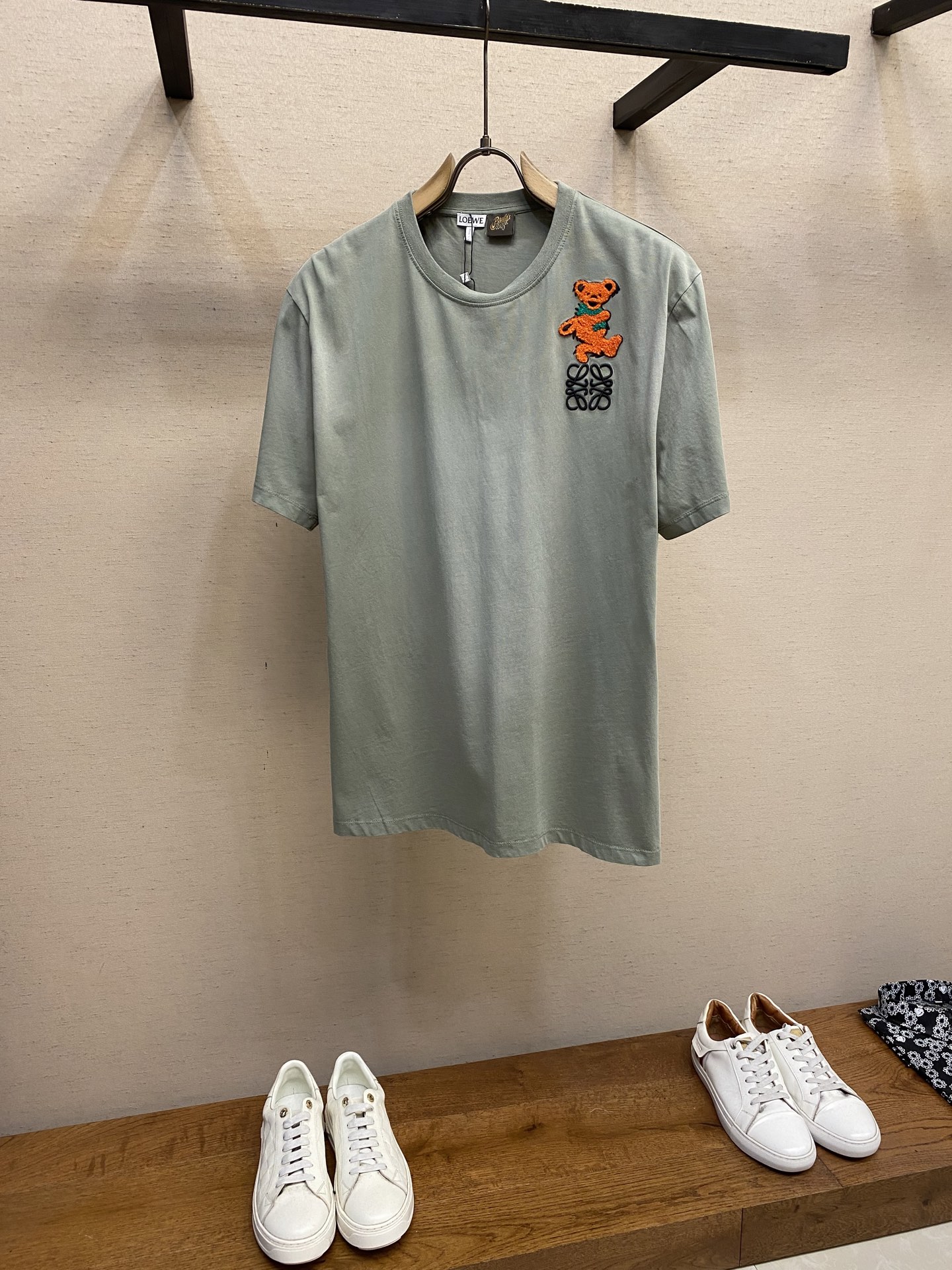 NO:445492,Loewe, Dancing Bear Embroidered Round Neck Short Sleeve Original, 200-plus Buy; Lightweight cotton T-shirt, loose fit, standard length, round neck design, chest with bear terry cloth embroidery, three-dimensional logo pattern, wash water to make aging, full set of auxiliary materials equipped # Lightweight pure cotton tight cotton fabric adopts 24S special textile tight cotton, 185g; matched with 32S1X1 tie-frame thread, 220g. Due to the relatively thin 24 yarns, the fabric may feel very soft, the texture is light and highly breathable. Through special spinning technology, the fabric has a unique texture and appearance; the tight structure makes the fabric more wear-resistant and wrinkle-resistant, and can maintain beauty and smooth for a long time. # Chest is decorated with bear terry cloth embroidery  Use embroidery threads suitable for the corresponding colors and thicknesses of the pairs; the embroidered terry cloth must be made of delicate materials and moderate thickness to ensure the embroidery effect and feel. During the embroidery process, you must control the strength to avoid wrinkling or damage to the terry cloth; at the same time, maintain the continuity and smoothness of the lines. Use scissors to trim off the excess thread and burrs to make the lines cleaner. # Logo logo embroidery adopts three-dimensional embroidery technology, and the letters clearly restore the spacing curve. Select mercerized embroidery threads with glossy sense, combined with complex embroidery needlework and fine detail processing, creating the embroidery effect of three-dimensional relief. Classic trademark letter design, fine needlework, clear font, and strong line and three-dimensional sense. # After-dressing sand making process  After the garment is frying, the new environmentally friendly garment process is transfected, dyed, washed and used. The fabric is dyed and processed by stone milling, and the garment is constantly immersed in the dye and rolled. The fabric is slightly faded after the garment is frying, and the color of the original fabric is changed to show nostalgic colors of different shades and shades. # Simple vertical round neck short-sleeved version. The paper pattern is developed with minimal body cut. The knitted material has certain extension performance and the upper body will not be tightly tied. The round neck is the same color ribbed splicing collar, and the inner sticking process of the back neck effectively prevents the neckline deformation after multiple washes, the fit shoulder line, the bottom swing and cuffs are tied. Size XS-L,,loewe,T-shirt,tees,t-shirt,alexander wang19860909Loewe,跳舞熊绣花圆领短袖 原,200购买；轻质棉质T恤、宽松版型、标准长度、圆领设计、胸前饰有小熊毛巾布刺绣、立体徽标图案、洗水做旧、全套辅料配备 # 轻质纯棉紧密棉面料 采用24S特纺织紧密棉,185g；搭配32S1X1拉架螺纹,220g.由于采用了相对较细的24支纱线,面料的手感可能非常柔软,质地轻薄并有高度透气性.通过特纺工艺,面料具有独特的纹理和外观；紧密的结构使得面料更加耐磨、抗皱,能够保持较长时间的美观和平整. # 胸前饰有小熊毛巾布刺绣 对版对色选用适合相应颜色和粗细的刺绣线；刺绣的毛巾布要求材质细腻,厚度适中,保证刺绣效果和手感选择.在绣花过程中,要控制好力度,避免力度过大导致毛巾布起皱或损坏；同时保持线条的连续性和流畅性.后整处理用剪刀修剪掉多余的线和毛刺,使线条更加整洁. # 标志徽标刺绣 采用立体刺绣工艺,字母清晰还原间距曲线.精选具有光泽感的丝光绣线进行,机结合复杂刺绣针艺,精细的细节处理,造就了立体浮雕的刺绣效果.经典商标字母设计,刺绣精细针法绵密,字体清晰且线条感和立体感强. # 成衣后炒砂做旧工艺 成衣后进行炒色工艺制作而成,成衣环保新工艺转染染色、洗水做旧.通过石磨的方式对面料进行染色加工,成衣不断地浸入染料中翻滚.炒砂后面料轻微掉色效果,改变原面料颜色呈现出深浅一明暗不同的怀旧色彩. # 简约垂直圆领短袖版型 对版纸样开发极简直身剪裁,针织材质具有一定延展性能,上身不会紧紧束身.圆领同色罗纹拼接领口,后领口内贴条工艺,有效防止多次穿洗后领口变形,合身肩线,底摆与袖口专机坎车明线收边. 尺码XS-L,,loewe,T-shirt,tees，t-shirt,alexander wang,Men's clothing