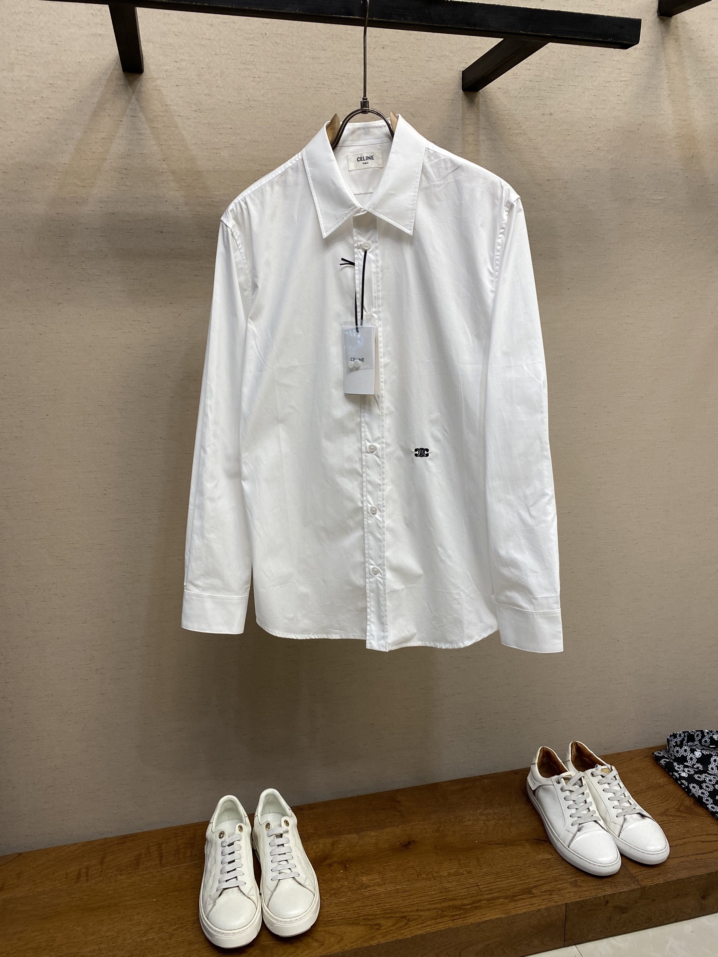 NO:411865,Celine, solid color embroidery shirt fabric selection is made into a thin and excellent breathable fabric through a weaving process with high warp and low weft density of cotton. The surface is smooth and smooth, and the touch is as smooth as silk. At the same time, the cotton is natural and skin-friendly, and it is comfortable and has no strange feeling. Because the warp yarns are tightly arranged, the fabric surface presents a longitudinal texture and soft luster, which enhances the visual sense of high-quality. Craft 1 The monochrome flat embroidery of the front piece controls the coordinated operation of the machine head, needle rod and spool through the high-precision computing system of the computer embroidery machine. The fabric frame moves accurately in horizontal and vertical directions to form a stitch trajectory, adjust the tension of the upper and lower lines to ensure that the stitch is flat and there is no floating line, forming a fine pattern with an error of ±0.1mm. Craft 2  The ironing master turned the collar upside down, ironed it from the bottom to the top through high temperature and humid steam, applied pressure to smooth the wrinkles, and then turned to the front and repeated the operation. Turn to the collar and burn it into a curve, and press the collar to the bottom to maintain a firmness. The rotator cuff part uses the hanging method to avoid crushing the edges. After adjusting the fiber density through the ironing master's 'push, return, and pull' technique, the shirt better fits the human body curve. Size S-XL, celine, shirts, alexander wang19860909Celine,纯色饰刺绣衬衫 面料选择 通过高支棉纱经密高,纬密低的织造工艺制成轻薄且具有极佳透气性的面料.表面光滑平整,触感如丝绸般柔滑,同时保留棉的天然亲肤性,贴身舒适无异样感.因经纱紧密排列,织物表面呈现纵向纹理与柔和光泽,强化视觉高级感. 工艺1 前片的单色平绣通过电脑绣花机高精度的计算系统控制机头、针杆、线轴的协同作业,布料框架在水平和垂直方向精准移动,形成针迹轨迹,调整上线和下线张力,确保线迹平整无浮线,形成误差在±0.1mm的精细图案 工艺2 熨烫师将衣领翻立,通过高温湿蒸汽从底部向上端熨烫,施加压力抚平褶皱,再翻至正面重复操作.转至领口烫出弧形,后领压至最底以保持挺括.肩袖部分利用悬空法避免压死边缘.通过熨烫师的“推、归、拔”技术调整纤维密度之后,使衬衫更好的贴合人体曲线 尺码S-XL,,celine,shirts,alexander wang,Men's clothing