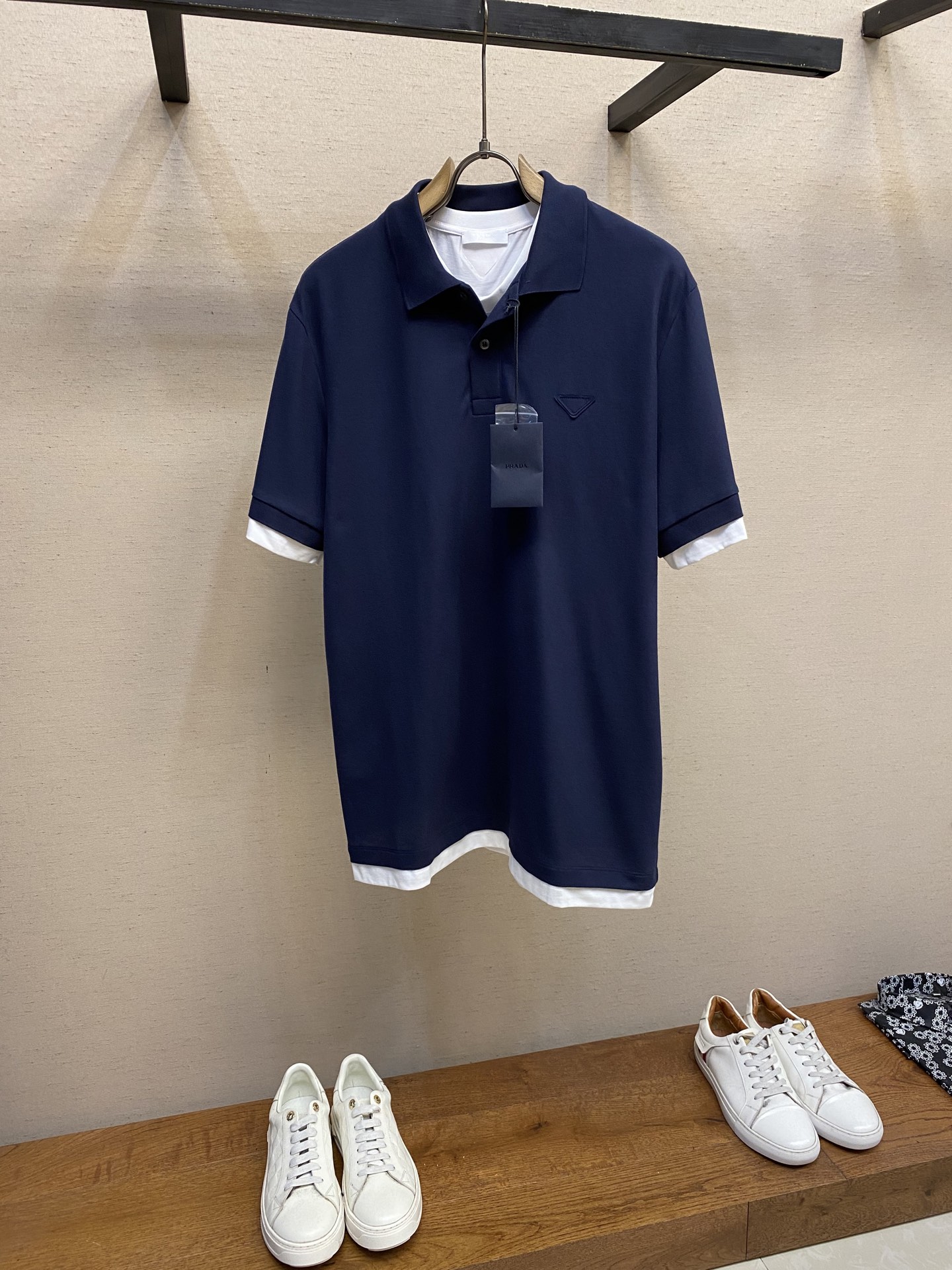 NO:418341,Prada contrast fabric triangle POLO shirt Fabric selection Choose beaded floor cloth woven by cotton fibers. Cotton fiber gives the fabric moisture absorption and breathability, skin-friendly and other characteristics. The surface of the beaded structure has concave and convex pores, which resembles a honeycomb, promotes air circulation and excellent heat dissipation efficiency. Because the elasticity of the cotton yarn is enhanced after being knitted by beads, it can still rebound after repeated stretching. Process 1 The rib knitted neckline is knitted using a double-needle bed, so that the coil alternates into a circle on the front and back surfaces, forming a 1*1 rib with longitudinal concave and convex texture. The elastic structure makes the neckline naturally fit the neck to avoid a sense of restraint. In addition, the double-layer sewing process links the body, which significantly reduces the probability and collapse of the neckline to expand into a 'ruffle edge' and maintains a long-term initial form. Process 2 By actively interfering with the shrinkage potential of cotton fibers, the fabric has been achieved from easy to change to stable, which improves dimensional stability, and is not easy to deform and wrinkle. Features Contrast jersey trim gives a sense of layering and enhances visual beauty. Size S-XL, prada, alexander wang19860909Prada饰撞色织物三角标POLO衫 面料选择 选用棉纤维编织而成的珠地布.棉纤维赋予面料吸湿透气,亲肤等特点.珠地结构表面呈现凹凸疏孔,形似蜂巢,促进空气循环,散热效率优良.因棉纱经珠地编织后弹性增强,反复拉伸仍可回弹. 工艺1 罗纹针织领口使用双针床编织,使线圈在正反面交替成圈,形成纵向凹凸纹路的1*1罗纹.弹性结构使领口自然贴合颈部,避免束缚感,加之双层缝纫工艺链接衣身,显著降低领口外扩成“荷叶边”的概率与塌陷,保持长久初始形态. 工艺2 通过主动干预棉纤维收缩潜能,实现了面料从易变到稳定的跨越,提升了尺寸稳定性,同时不易变形,褶皱. 特点 撞色平纹针织饰边赋予层次感,同时强化视觉美感. 尺码S-XL,,prada,alexander wang,Men's clothing