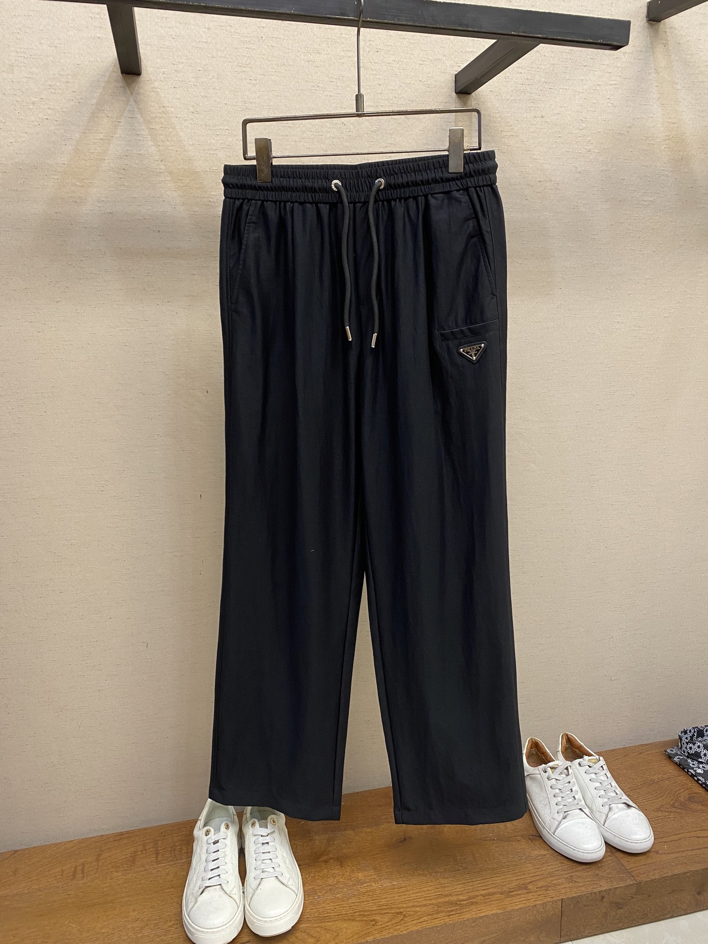 NO:471979,Prada, PD Tencel Linen Elastic Waist Drawstring Casual Pants On the fashionable and comfortable track, this Tencel Linen Elastic Waist Drawstring Casual Pants is undoubtedly a well-deserved leader. It redefines the standards of high-end casual pants with exquisite craftsmanship and unique design. Selection of Tencel and linen blend fabrics perfectly combines the smoothness of Tencel and the texture of the hemp. Tencel fiber brings a silk-like delicate touch, gently sticking to the skin, as comfortable as the second layer of skin; the hemp material gives the fabric natural texture and breathability, and can quickly expel moisture and keep the legs dry even in the stuffy season. This fabric combination is not only comfortable, but also has an excellent drape, making the pants look natural and smooth, showing elegance while walking.  The waist is made of elastic straps and drawstrings, which is a model of comfort and practicality. The high elastic elastic waist can perfectly fit all kinds of waist circumferences without being tight and easy to wear. The metal decorative head at the end of the drawstring is carefully polished and has a high gloss, which not only adds the exquisiteness of details, but also demonstrates the brand's ultimate pursuit of quality. The metal triangle logo on the front and rear pockets is a symbol of PR** identity. The logo is made of high-quality metal material and is finely polished to present a low-key and luxurious luster. Size XS-L, prada, alexander wang19860909Prada,PD天丝亚麻松紧腰抽绳 休闲裤 在时尚与舒适的赛道上,这款天丝麻松紧腰抽绳休闲裤无疑是当之无愧的领跑者,它以精湛工艺与独特设计,重新定义高端休闲裤的标准.甄选天丝与麻混纺面料,将天丝的柔滑与麻料的质感完美融合.天丝纤维带来丝绸般的细腻触感,轻柔贴肤,如第二层肌肤般舒适；麻料则赋予面料天然的纹理与透气性,即使在闷热的季节,也能快速排出湿气,保持腿部干爽.这种面料组合不仅舒适,还具有出色的垂坠感,让裤型自然流畅,行走间尽显优雅. 腰部采用松紧带与抽绳双结合的设计,堪称舒适与实用的典范.高弹性的松紧腰头能完美贴合各种腰围,不紧不勒,穿着自在.抽绳末端的金属饰头,经过精心打磨,光泽度高,不仅增加了细节的精致感,更彰显品牌对品质的极致追求.前侧口袋和后侧口袋上的金属三角徽标,是PR**身份的象征.徽标采用高品质金属材质,经过精细抛光处理,呈现出低调而奢华的光泽. 尺码XS-L,,prada,alexander wang,Men's clothing