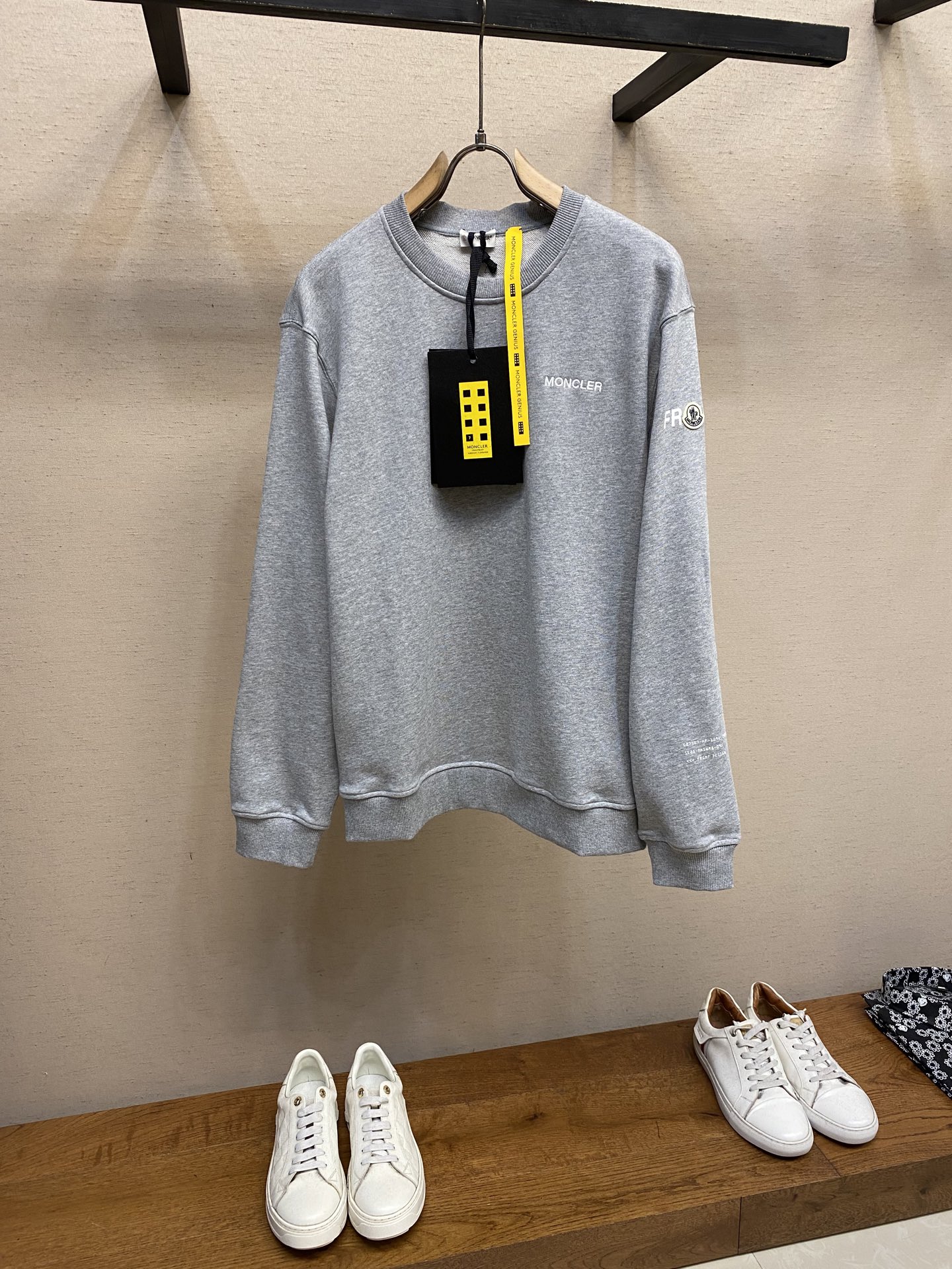 NO:527867,Moncler, printed round neck sweater fabric selection is a single-sided fish scale fabric made of cotton as a base, with a smooth knitted surface on the front, and the touching surface is formed by the floating thread knitting technology of the knitting machine to form a three-dimensional terry loop, which increases the fluffy feeling and is delicate at the same time. The terry loop structure absorbs a large amount of water and evaporates quickly, and it is not easy to deform after multiple washings. Process 1 The high-saturation pattern is presented on the fabric through glue printing, and the scraper pressure is uniform. It is scraped in 3 times to ensure that the glue penetrates and covers it fully. After high-temperature curing, the pigment and cotton fibers are firmly combined. The ink-absorbing and penetration characteristics of the cotton fibers make the pattern not easily fall off due to friction. Process 2  The 2*2 ribs formed by alternately configuring the vertical rows of the front coil and the reverse coil are still very elastic, with wide textures, fitting the wrist and waist without any sense of restraint. The gaps between the coils allow air circulation while not losing warmth. Process 2 Through active intervention in the shrinkage potential of cotton fibers, the fabric has been achieved from easy to change to stable, improving dimensional stability, and not easily deforming or wrinkling. Size S-XL, hoodie, sweatshirts, alexander wang19860909Moncler,印花圆领卫衣 面料选择 采用棉为基底编织而成的单面鱼鳞布面料,正面为平滑的针织面,触肤面通过针织机的浮线编织技术形成立体的毛圈,增加蓬松感, 同时触感细腻.毛圈结构吸水量大且蒸发快,多次洗涤不易松散变形. 工艺1 通过胶浆印花在面料上呈现4处高饱和度图案,刮刀压力均匀,分3次刮印确保胶浆充分渗透并覆盖.再通过高温固化后,颜料与棉纤维结合牢固,棉纤维的吸墨渗透特性使图案不易因摩擦导致脱落. 工艺2 通过正面线圈纵行和反面线圈纵行相互交替配置而形成的2*2罗纹,弹性依然很好,纹路较宽,贴合腕部和腰部而无束缚感,线圈间的空隙允许空气流通,同时不失保暖性能. 工艺2 通过主动干预棉纤维收缩潜能,实现了面料从易变到稳定的跨越,提升了尺寸稳定性,同时不易变形,褶皱. 尺码S-XL,,hoodie,sweatshirts,alexander wang,Men's clothing