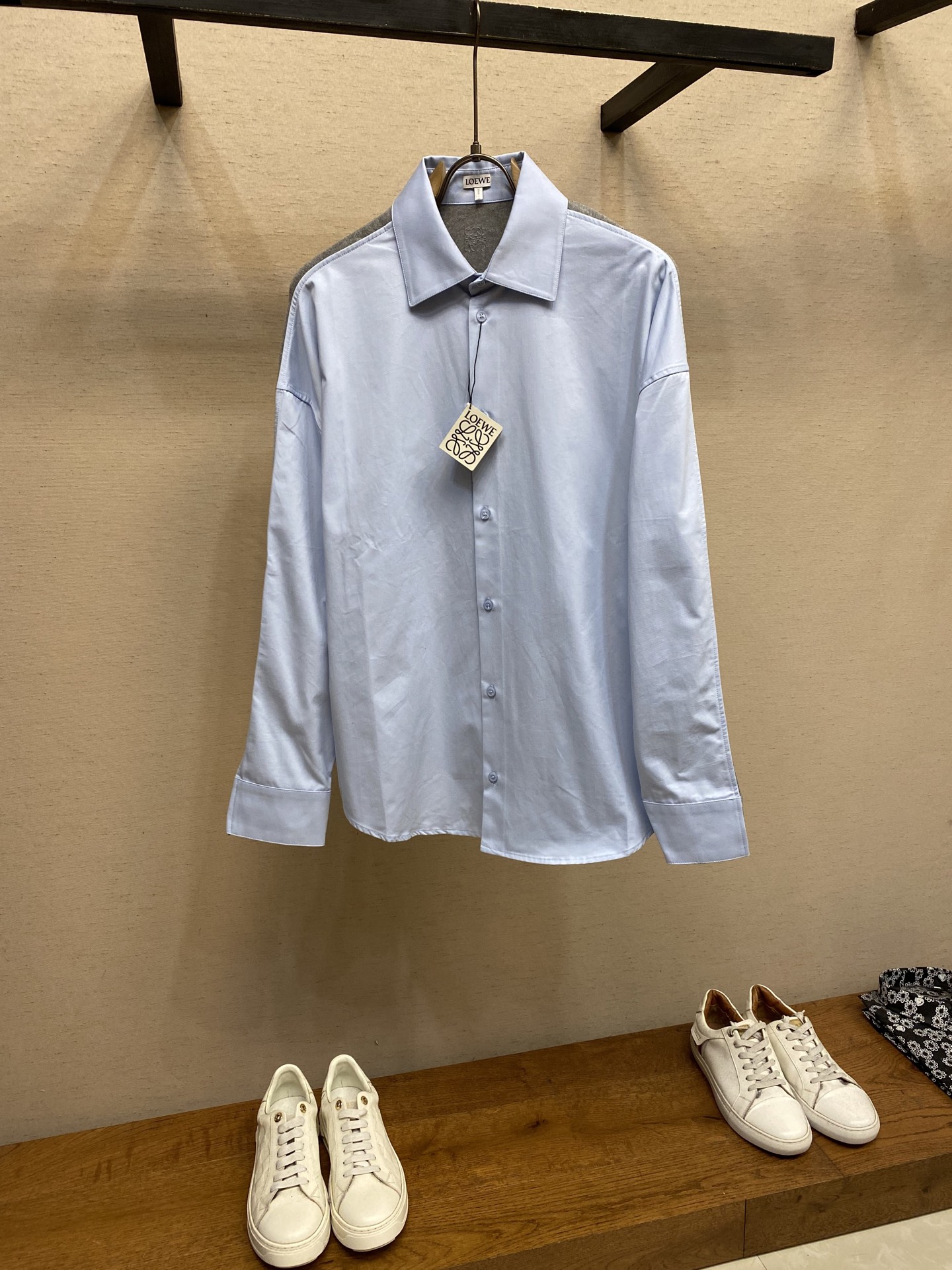 NO:574029,Loewe, cotton and knitted patchwork shirt. Fabric 1 choice. The front panel is made of high-count cotton yarn through a weaving process with high warp density and low weft density. It is made into a light and extremely breathable fabric. The surface is smooth and smooth, and feels as smooth as silk. It also retains the natural skin-friendly properties of cotton, making it comfortable and comfortable next to the body without any strange feeling. Because the warp yarns are closely arranged, the surface of the fabric shows a longitudinal texture and soft luster, which enhances the visual sense of luxury. Fabric 2 choice  The back panel is woven with extremely fine wool yarn through high-count spinning technology into a moderately dense fabric that is soft to the touch and skin-friendly, with a delicate velvet feel on the surface. The wool fiber has a natural hollow structure, which can lock in still air and form an excellent thermal insulation layer. Even if it is light and thin, it has a good thermal insulation effect. Process 1   Under the back collar, the high-precision calculation system of the computerized embroidery machine controls the coordinated operation of the machine head, needle bar, and thread spool. The fabric frame moves accurately in the horizontal and vertical directions to form a stitch track. The upper and lower thread tensions are adjusted to ensure that the stitches are smooth and free of floating threads, forming anagram embroidery with an error of ±0.1mm. Process 2  The ironer turns the collar up, irons it from the bottom to the top with high-temperature and moist steam, applies pressure to smooth out the wrinkles, and then turns it over to the front and repeats the operation. Turn to the collar to iron out an arc, and press the back collar to the bottom to keep it stiff. The rotator sleeves are suspended to avoid crushing the edges. After adjusting the fiber density through the ironer's 'push, return, and pull' technology, the shirt can better fit the body curve.  Size 36,38,40,42,,loewe,shirts,alexander wang19860909Loewe、棉质和针织拼接衬衫 面料1选择 前片选用高支棉纱通过经密高,纬密低的织造工艺制成轻薄且具有极佳透气性的面料.表面光滑平整,触感如丝绸般柔滑,同时保留棉的天然亲肤性,贴身舒适无异样感.因经纱紧密排列,织物表面呈现纵向纹理与柔和光泽,强化视觉高级感. 面料2选择 后幅通过高支纺纱技术,用极细的羊毛纱线织成密度适中的面料,触感柔软亲肤,表面有细腻的绒感.羊毛纤维特性具有天然的中空结构,能锁住静止空气,形成绝佳的隔热层,即使轻薄,也有良好的保暖效果. 工艺1 后领下方处通过电脑绣花机高精度的计算系统控制机头、针杆、线轴的协同作业,布料框架在水平和垂直方向精准移动,形成针迹轨迹,调整上线和下线张力,确保线迹平整无浮线,形成误差在±0.1mm的anagram刺绣. 工艺2 熨烫师将衣领翻立,通过高温湿蒸汽从底部向上端熨烫,施加压力抚平褶皱,再翻至正面重复操作.转至领口烫出弧形,后领压至最底以保持挺括.肩袖部分利用悬空法避免压死边缘.通过熨烫师的“推、归、拔”技术调整纤维密度之后,使衬衫更好的贴合人体曲线. 尺码36,38,40,42,,loewe,shirts,alexander wang,Men's clothing