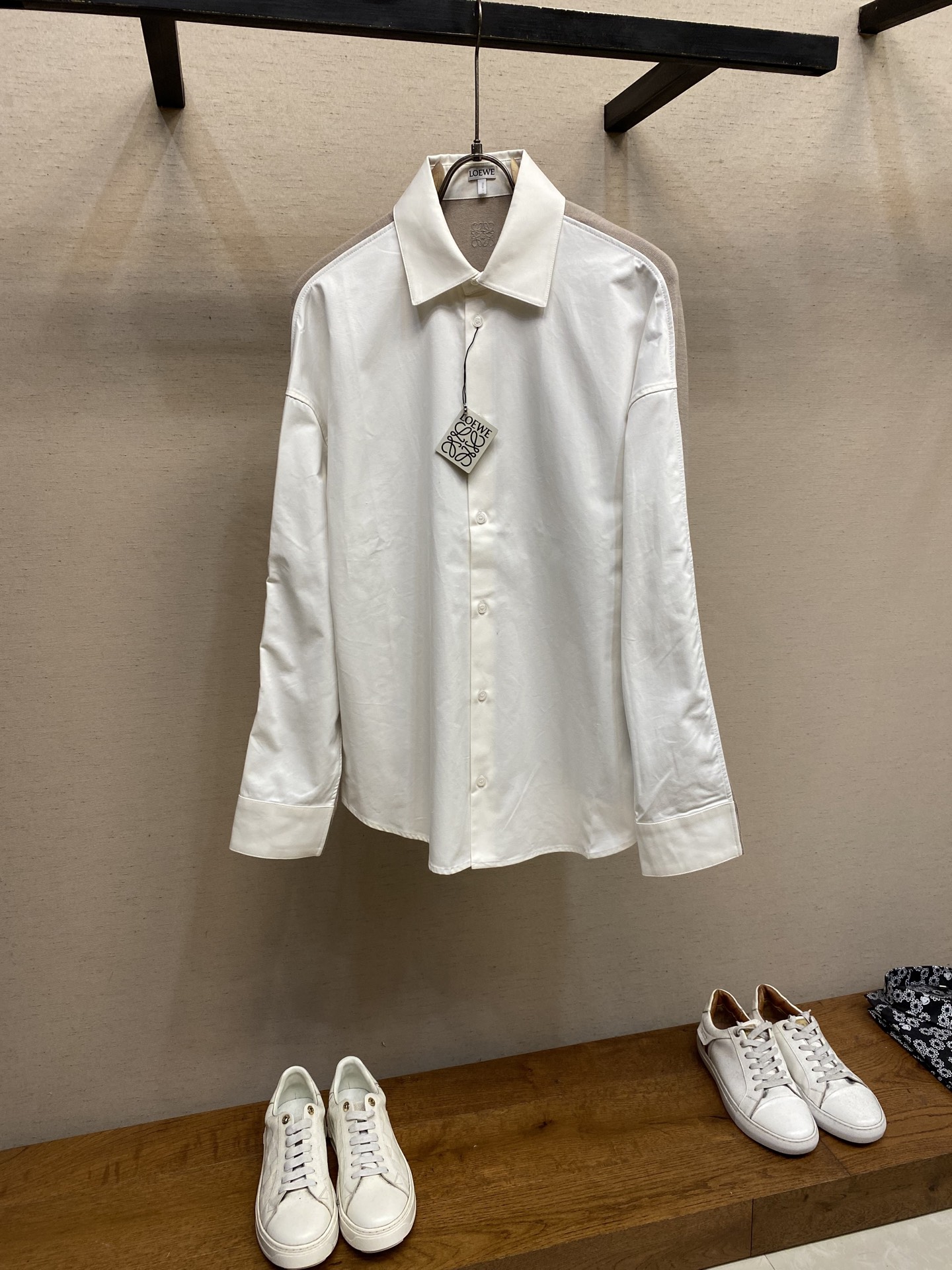 NO:528903,Loewe, cotton and knitted splicing shirt Fabric 1 Selection The front sheet is made of high-split cotton yarns and made of light and excellent breathable fabrics through a weaving process with high warp and low weft density. The surface is smooth and smooth, and the touch is as smooth as silk. At the same time, the cotton is natural skin-friendly and comfortable, and it is not unusual. Because the warp yarns are tightly arranged, the fabric surface presents a longitudinal texture and soft luster, which enhances the visual sense of high-quality. Fabric 2 Selection The back sheet is made of high-split spinning technology, and is woven into a moderately dense fabric with soft and skin-friendly touch, with a delicate velvet feel. The wool fiber has a natural hollow structure, which can lock in stationary air and form an excellent heat insulation layer. Even if it is light and thin, it has a good warming effect. Craft 1  The collaborative operation of the head, needle rod and spool is controlled by a high-precision computing system of the computer embroidery machine. The fabric frame moves accurately in horizontal and vertical directions to form a stitch trajectory, adjust the tension of the upper and lower lines to ensure that the stitch is flat and has no floating lines, forming an anagram embroidery with an error of ±0.1mm. Craft 2 The ironing master turns the collar upward, irons from the bottom to the upper end through high temperature and humid steam, applies pressure to smooth the wrinkles, and then turns to the front and repeat the operation. Turn to the collar to burn out the arc, and press the back collar to the bottom to maintain a crispness. The rotator cuff part uses the suspension method to avoid crushing the edges. After adjusting the fiber density through the ironing master's 'push, return, and pull' technology, the shirt better fits the human body curve. Size 36, 38, 40, 42, , loewe, shirts, alexander wang19860909Loewe、棉质和针织拼接衬衫 面料1选择 前片选用高支棉纱通过经密高,纬密低的织造工艺制成轻薄且具有极佳透气性的面料.表面光滑平整,触感如丝绸般柔滑,同时保留棉的天然亲肤性,贴身舒适无异样感.因经纱紧密排列,织物表面呈现纵向纹理与柔和光泽,强化视觉高级感. 面料2选择 后幅通过高支纺纱技术,用极细的羊毛纱线织成密度适中的面料,触感柔软亲肤,表面有细腻的绒感.羊毛纤维特性具有天然的中空结构,能锁住静止空气,形成绝佳的隔热层,即使轻薄,也有良好的保暖效果. 工艺1 后领下方处通过电脑绣花机高精度的计算系统控制机头、针杆、线轴的协同作业,布料框架在水平和垂直方向精准移动,形成针迹轨迹,调整上线和下线张力,确保线迹平整无浮线,形成误差在±0.1mm的anagram刺绣. 工艺2 熨烫师将衣领翻立,通过高温湿蒸汽从底部向上端熨烫,施加压力抚平褶皱,再翻至正面重复操作.转至领口烫出弧形,后领压至最底以保持挺括.肩袖部分利用悬空法避免压死边缘.通过熨烫师的“推、归、拔”技术调整纤维密度之后,使衬衫更好的贴合人体曲线. 尺码36,38,40,42,,loewe,shirts,alexander wang,Men's clothing