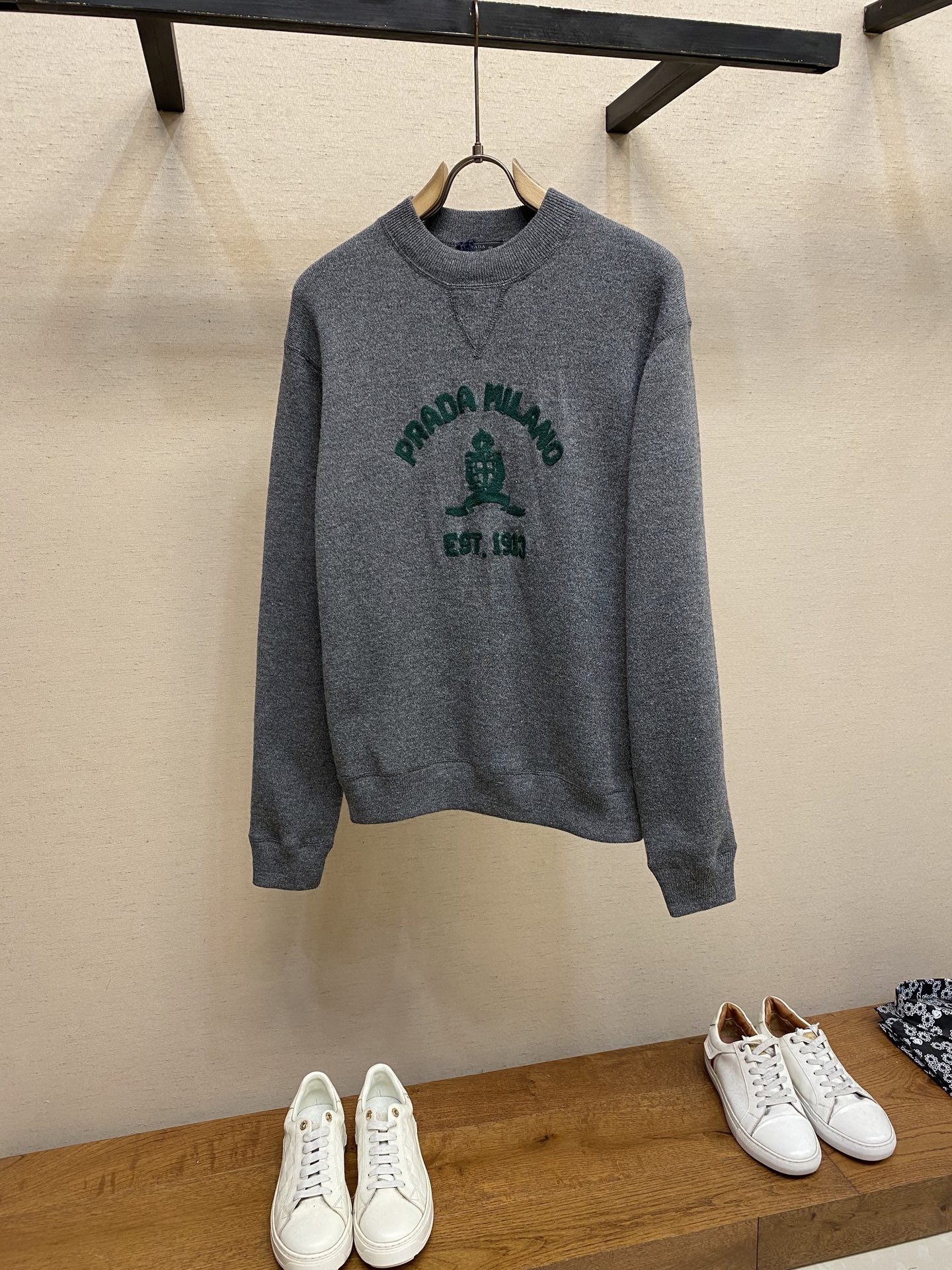 NO:574020,Prada, music logo embroidered knitted sweater, original purchase, 400; flat knit design, embroidered logo embellishment, regular fit, rib knitted crew neck, regular shoulders, rib knitted cuffs and hem, full set of accessories # blended specific floral gray wool 14 needles high count fine gauge  The core process index of 14 knitting machines adopts advanced equipment with high needle count and fine gauge. The knitted stitches are denser, thus creating a sweater body with fine texture, light weight, softness and good drape. # Iconic design details V-shaped threaded neckline  The 'V-shaped design thread' on the neckline is by no means an ordinary stitch, but a functional and decorative craft. Through precise weaving or stitching technology, a clear V-shaped visual guide is formed on the neckline, which effectively modifies the neck and face lines and extends the visual effect. # Three-dimensional decorative core chain towel embroidery   Highlights of the chain-type towel embroidery process. Special embroidery techniques form a continuous, raised towel-like loop effect through repeated chain stitches. The pattern appears on the cloth with a strong three-dimensional effect, soft and fluffy to the touch, and is highly recognizable. It presents a towel-like texture, forming an interesting contrast with the smooth bottom surface of the sweater, enriching the visual and tactile layers. The chain structure makes the embroidery not easy to snag or fall off, and has good durability # Classic round neck standard version  The neckline, cuffs and hem are all ribbed; the excellent lateral elasticity of the ribbed tissue not only ensures that the key parts of the garment are firm, not easily deformed, durable and washable, but can also be tightened naturally to outline neat contours. Its functionality and decorative properties not only prevent the intrusion of cold wind, improve thermal efficiency, but also add a sense of rhythm to the details of the overall simple design, making the silhouette more crisp.   Size XS-L,,prada,sweaters,alexander wang19860909Prada、音乐徽标刺绣针织毛衣 原,400购买；平针针织设计、刺绣徽标点缀、常规版型、罗纹针织圆领、常规肩部、罗纹针织袖口和下摆、全套辅料配备 # 混纺特定花灰毛料14针高支细针距 14针织机核心工艺指标,采用了高针数、细针距的先进设备.编织的针脚更密集,从而打造出质地细腻、轻薄柔软且垂坠感佳的毛衣本体. # 标志性设计细节V字走线领口 领口的“V字设计走线”绝非普通缝线,而是一种具有功能性与装饰性的工艺.通过精准的编织或缝线技术,在领口形成清晰的V形视觉导向,有效修饰颈部与脸型线条,延伸视觉效果. # 立体装饰核心锁链式毛巾刺绣 锁链式毛巾刺绣质工艺亮点,特殊的刺绣技法,通过重复的链式针迹形成连续、凸起的毛巾状线圈效果. 图案跃然布上立体感极强,触感柔软蓬松,极具辨识度.呈现出类似毛巾料的肌理,与平滑的毛衣底面形成有趣对比,丰富视觉与触觉层次.链式结构使绣花不易抽丝或脱落,耐用性好 # 经典圆领标准版型 领口、袖口及下摆全部采用罗纹收口；利用罗纹组织优异的横向弹性,不仅确保了衣身关键部位牢固不易变形、耐穿耐洗,同时能自然收紧,勾勒出利落的轮廓线条.其功能性与装饰性并存既防止冷风灌入,提升保暖效率,又为整体简约设计增添了细节上的节奏感,使版型更挺括. 尺码XS-L,,prada,sweaters,alexander wang,Men's clothing