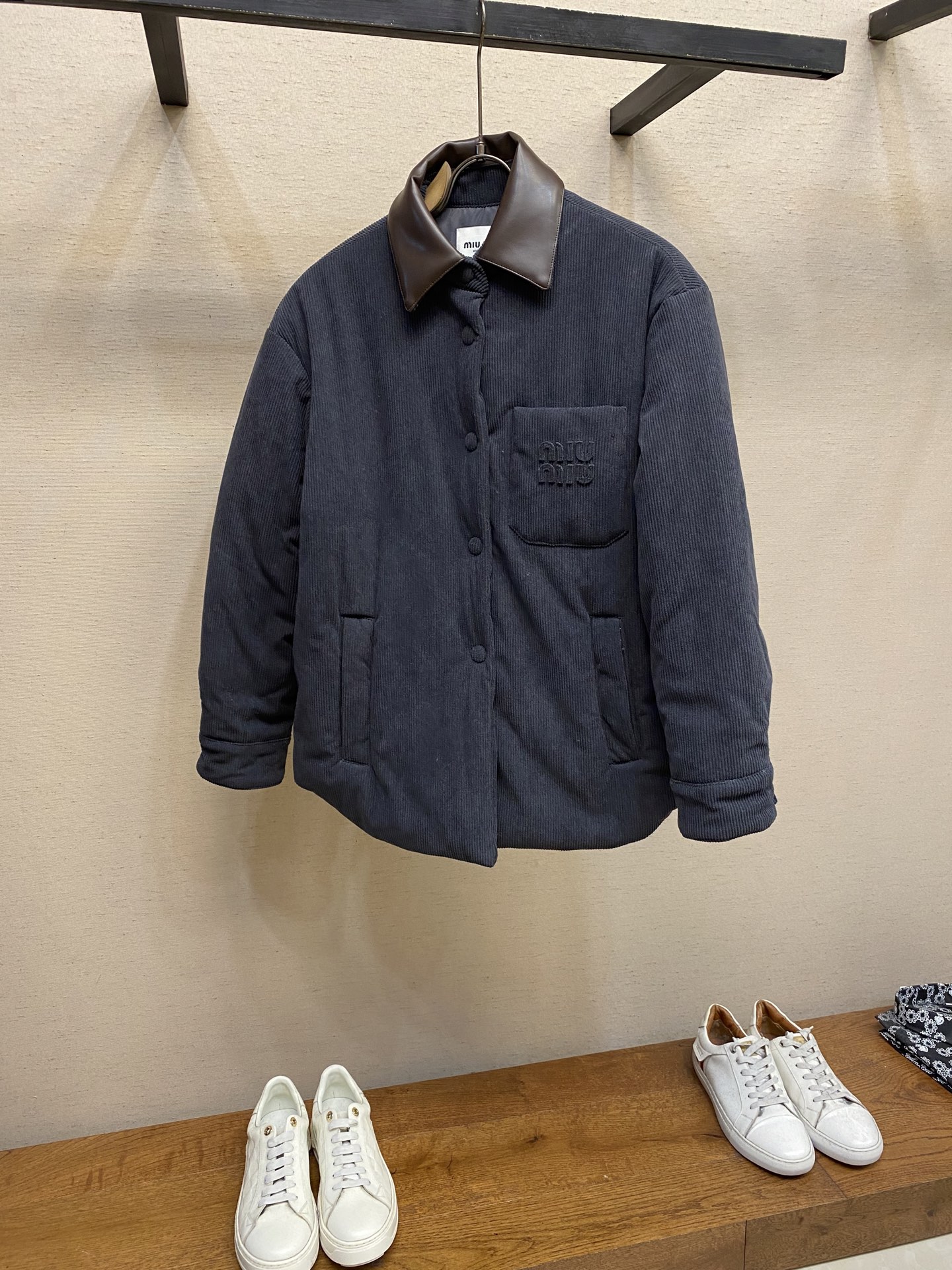 NO:569416,Miu Miu Leather Collar Corduroy Down Jacket When the same color embroidery quietly grows among the corduroy textures - MIUMIU redefines winter elegance with 'hidden beauty', making warmth a tacit whisper.  Classic fine-ribbed corduroy wraps the body, and down is like clouds lurking between the concave and convex warp and weft. 90 white duck down silently resists the cold wind, but lets the fabric speak for itself - every velvet is the path of sunlight, and every ridge is a fortress built by warmth.  The customized lambskin lapel descends along the curve of the neck, making it breathable like a second layer of skin. Cool leather and soft suede complete a material game at the collar, and the sound of metal snaps opening and closing becomes the only punctuation mark in this conversation.   Exquisite appliqué craftsmanship performs visual magic on the left breast pocket. The embroidered fabric of the same color as the fabric runs along the MIUMIU logo, and only the subtle gloss difference and raised stitches reveal the secret. Only the touch of fingertips or the refraction of light at a specific angle can one decipher the Morse code written to the soul. Sizes S, M, L,, miumiu, down jacket, sheepskin, alexander wang19860909Miu Miu 皮领灯芯绒羽绒服 当同色绣花在灯芯绒纹路间悄然生长——MIUMIU以「隐迹之美」重新定义冬日优雅,让温暖成为一场心照不宣的私语. 经典细棱灯芯绒包裹身躯,羽绒如云朵潜伏于凹凸经纬之间.90白鸭绒无声抵御寒风,却让面料自己说话——每一道绒沟都是日光走过的轨迹,每一条棱线都是温暖筑起的堡垒. 定制的小羊皮翻领沿颈项曲线降落,如第二层肌肤般贴合呼吸.冷冽皮革与柔软绒面在领口完成一场材质博弈,金属按扣开合声成为这场对话里唯一的标点符号. 精致的贴布绣工艺在左胸口袋上演视觉魔法与面料完全同色的绣布沿MIUMIU标识游走,仅以微妙的光泽差与针脚凸起泄露天机.须得指尖触碰,或是特定角度的光线折射,方能破译这枚写给知音者的摩斯密码. 尺码S,M,L,,miumiu,down jacket,sheepskin,alexander wang,Men's clothing