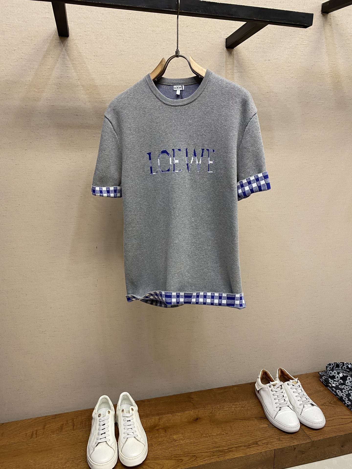 NO:573003,Loewe, lined sleeves woolen short sleeves, available in gray, brown, original, 500; blended wool and cotton, jacquard lettering on the front, decorated with plaid jacquard, regular fit, standard length, piqué jacquard stitching, crew neck fit # blended wool and cotton wool body  It uses yarn blended between wool and cotton, processed by 12S knitting jacquard machine; it cleverly combines the advantages of the two fibers. The wool component brings excellent warmth, natural elasticity and drape, while the cotton provides skin-friendly and breathable comfort, and balances the itch that pure wool may bring.   Using the tiny dot-like texture of sesame base jacquard as the base, a unique micro-texture is formed on the surface of the fabric, which not only increases the visual level, but also makes the touch delicate and plump. The final product achieves a light and compact texture, ensuring that it has a sense of weight but is not heavy when worn. # Woolen Jacquard Technology Design  The jacquard pattern is the design of this product. The imported 12S jacquard machine is used for weaving, which can control the yarn with extremely high precision, thereby weaving complex patterns with clear patterns and rich details. The front brand logo and plaid pattern are directly formed by yarns of different colors during the weaving process. This process makes the pattern and the fabric itself integrated without any additional touch, and is strong and durable and will not fall off. # Standard round neck version   The style adopts the regular version and standard length, striving to restore the classic tailoring that fits well and is easy to match, and can adapt to the body shape of most consumers. The neckline is made of pit stitching technology to make a round neck and pique weave, which is more elastic and wear-resistant than ordinary plain knitting. It can effectively prevent the neckline from deforming or loosening after being worn and taken off many times, and the details are processed with precision. Sizes XS-L,, loewe, T-shirt, alexander wang19860909Loewe,内格翻袖毛织短袖 发售色系灰色、棕色 原,500；混纺羊毛棉质、正面饰有提花字母,饰有格纹提花、常规版型、标准长度、珠地提花缝线、圆领版型 # 混纺羊毛棉质毛织主体 采用羊毛与棉混纺的纱线,12S针织提花机处理；巧妙地结合了两种纤维的优点.羊毛成分带来了优异的保暖性、天然弹性和悬垂感,而棉质则提供了亲肤透气的舒适度,并平衡了纯羊毛可能带来的刺痒感. 通过芝麻底提花这种细小的点状纹理作为基底,面料表面形成了独特的微肌理,不仅增加了视觉层次,更使触感细腻丰盈.最终成品实现了轻盈紧凑的质感,确保了穿着时既有分量感又不显厚重. # 毛织提花工艺设计 提花图案是本品的设计,运用进口12S提花机进行织造,能够以极高的精度控制纱线,从而织出图案清晰、细节丰富的复杂花纹.正面品牌标识与格纹图案均,直接由不同颜色的纱线在织造过程中一体成型.这种工艺使图案与面料本身浑然一体,无任何附加触感,且牢固耐用,不会脱落. # 标准圆领版型 款式采用常规版型与标准长度,力求还原合身且易于搭配的经典剪裁,能适应大多数消费者的身形.领口采用坑条缝线工艺制成圆领,珠地组织,比普通平纹针织更具弹性与耐磨性,能有效防止领口在多次穿脱后发生变形或松懈,细节处理精细到位. 尺码XS-L,,loewe,T-shirt,alexander wang,Men's clothing