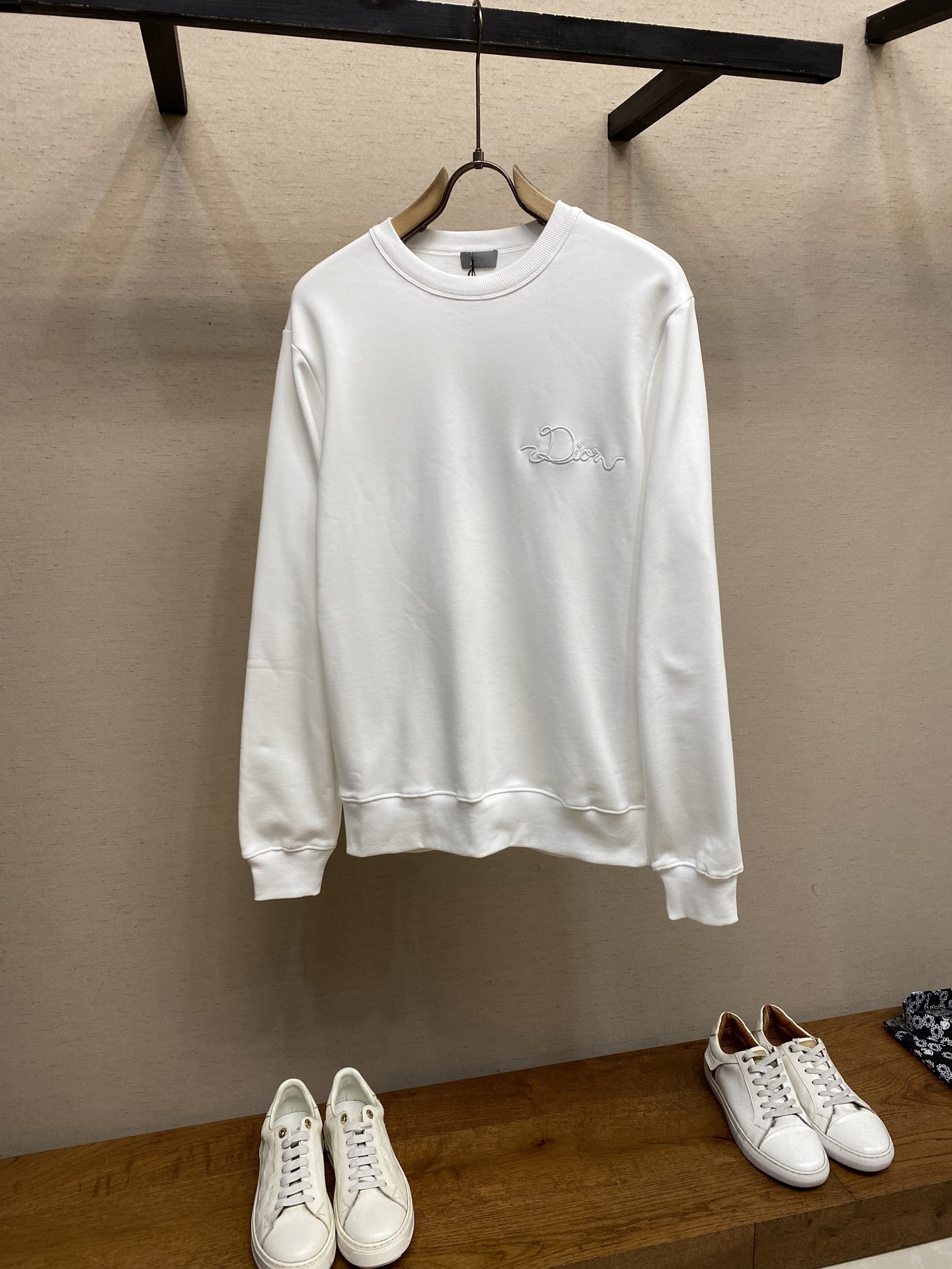 NO:599591,Dior, CD / Ribbon logo round neck sweatshirt. Fabric 26 count double yarn count terry fabric / 380G rib 21 count 2x2 rib / 380G This sweatshirt is a new product of the 2026 spring men's wear series, decorated with Ribbon  The logo pays homage to the craftsmanship of the workshop. Crafted from white cotton fleece, it features a ribbed crew neck, cuffs and hem. The relaxed silhouette pairs well with oversized trousers.  It adopts a composite structure of 26 double-yarn top and bottom yarn terry, and uses a precision raising process to form a uniform suede on the inside, achieving a velvet-like skin-friendly touch. The heavy weight gives the fabric a sculptural stiffness, perfectly balancing the lazy silhouette and clean lines. The collar/cuffs are made of 21-count 2×2 reinforced ribs, and are woven in both warp and weft directions to form a memory elastic network, ensuring that the original fit can be maintained after multiple wears and takeoffs.  The process uses laser-cut ribbons and micron-level hot-melt composite technology, and is processed through positioning embroidery technology. The edges achieve seamless fit with precision, and the decorative ribbon is fixed on the chest. Its luster forms a subtle light and shadow dialogue with the cotton matte base, and the pattern is restored to the detailed specifications. Sizes XS-L, dior, hoodie, sweatshirts, alexander wang19860909Dior、CD / Ribbon 标志圆领卫衣 面料26支双纱支底纱的毛圈绒面料 / 380G 罗纹21支 2x2 罗纹 / 380G 这款卫衣是二零二六春季男装系列新品,饰以Ribbon 标志,向工坊的精湛工艺致敬.采用白色棉质起绒面料精心制作,搭配罗纹圆领、袖口和底边.休闲廓形,可与超大版型长裤搭配. 采用26支双纱面层支底纱毛圈的复合结构,通过精密起绒工艺在内侧形成均匀绒面,实现天鹅绒般亲肤触感.重磅克重赋予面料雕塑般挺括感,完美平衡慵懒廓形与利落线条.领口/袖口采用21支2×2强化罗纹,以经纬双向编织形成记忆弹性网,确保多次穿脱仍保持初始贴合度. 工艺采用激光切割缎带与微米级热熔复合技术,通过定位刺绣工艺处理.边缘实现精度的无缝贴合,装饰带固定于前胸,其光泽与棉质哑光基底形成微妙的光影对话,对版还原细节规格. 尺码XS-L,,dior,hoodie,sweatshirts,alexander wang,Men's clothing