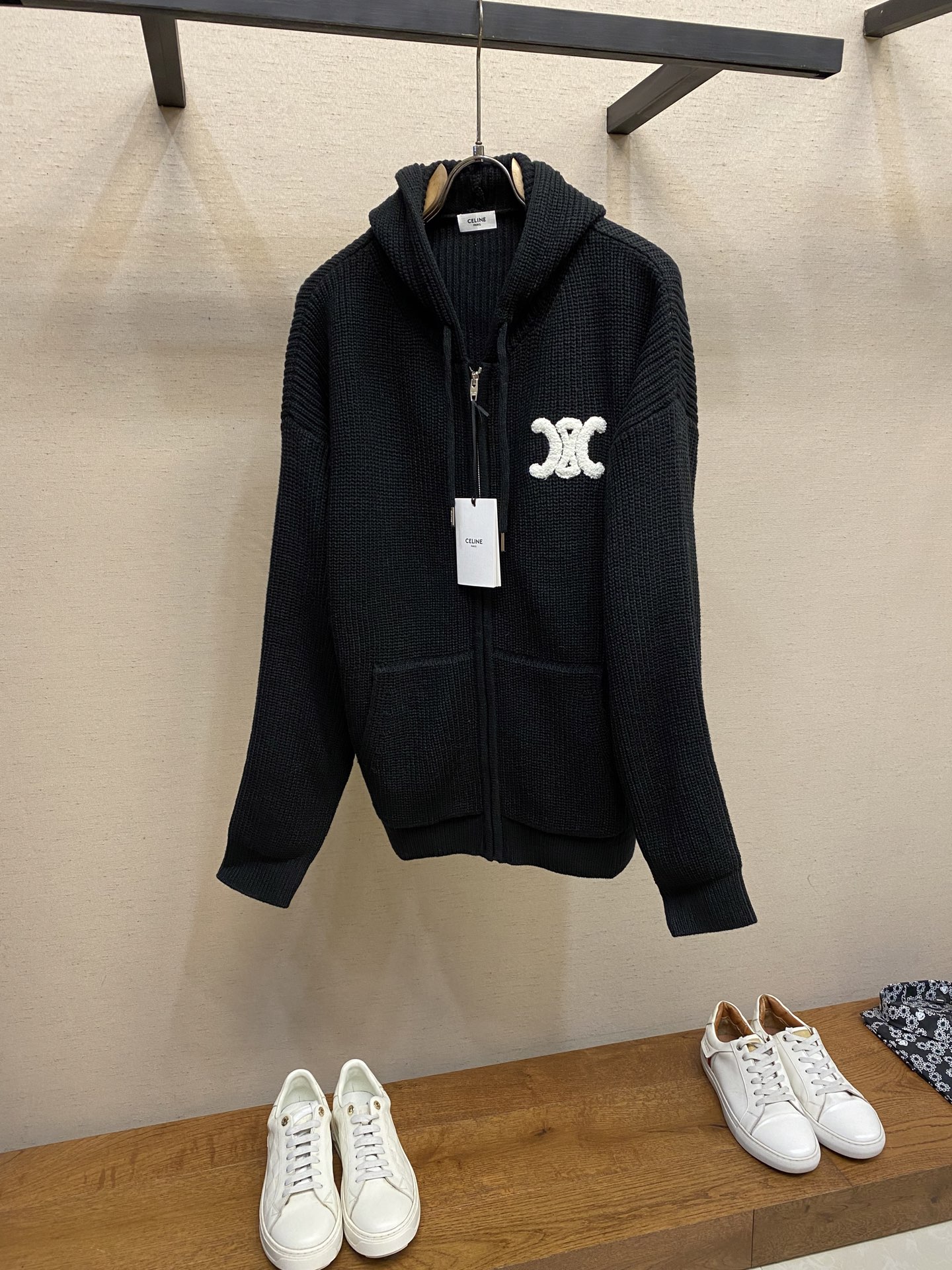 NO:623991,Celine, woolen hooded sweatshirt 1. The main knitted fabric is made of ultra-fine merino wool. The characteristic yarn count is 26S/2 (medium-thick knitted yarn), double-twisted to ensure that the fabric is stiff and soft; the combing process is used to remove short fibers, the surface is smooth and free of stray hairs, and the hand feels delicate and does not stick to the body. The color is light gray and black, and the soft gray level is achieved through the mixed color spinning process (white + dark gray fibers are mixed in proportion) to avoid the monotony of solid colors.  2. Ribbed detail fabric (2 × 2 tight ribs on the collar, cuffs, and hem, using high-elastic spandex) to ensure excellent resilience after stretching, not easy to deform, and fit the body curve. 2. The core production process combines the knitted structure with the three-dimensional silhouette 1. The main knitting process Flat Knitting uses a computerized flat knitting machine (such as the Stoll CMS series) to knit the body and sleeves in one piece, reducing seams and improving comfort. 2.  Brand logo technology (chest embroidery) The white pattern of the three-dimensional towel embroidery is made of 8 strands of pure cotton towel thread, which is produced by a computer embroidery machine with a 3D padding embroidery process. The stitch density is ≥120 stitches/cm, and the edges are trimmed with Satin Stitch to ensure that the pattern is full and three-dimensional and not easy to fluff. The distance between the center of the pattern and the central axis of the zipper and the edge of the hem needs to be calibrated through a template, and the error is ≤0.5cm to ensure visual symmetry. Main body splicing  Seamless Joining (Seamless Joining) The main components such as the body and sleeves are woven in one piece using a flat knitting machine. There are only a few seams at the armpits and shoulder lines. The seams are processed with a 3-needle five-thread overlock sewing machine. The seam width is ≤0.8cm. After the edges are trimmed, they are hot-pressed and shaped to ensure that the splices are smooth and without bulges.  The shoulders are reinforced with twill silk strips (length 15cm, width 1.5cm) sewn on the inside of the shoulder line and fixed by hand quilting to enhance the load-bearing capacity of the shoulders and prevent the shoulder line from sagging after long-term wear. Sizes S-XL,,celine,hoodie,sweatshirts,real silk,hats,alexander wang19860909Celine,毛织连帽卫衣  1. 主体针织面料 材质超细美利奴羊毛 特性纱线支数26S/2（中粗针织纱）,双股并捻,确保面料挺括且柔软；采用精梳工艺去除短纤维,表面光洁无杂毛,手感细腻不扎身. 颜色浅灰色黑色,通过混色纺纱工艺（白色+深灰色纤维按比例混合）实现柔和的灰度层次,避免纯色单调感. 2. 罗纹细节面料 领口、袖口、下摆处为2×2紧密罗纹,采用高弹氨纶）确保拉伸后回弹性能优异,不易变形,且贴合身体曲线. 二、核心生产工艺针织结构与立体廓形的结合  1. 主体针织工艺 横机编织（Flat Knitting）采用电脑横机（如Stoll CMS系列）一体编织衣身、袖子,减少接缝提升舒适度.  2. 品牌标识工艺（胸前刺绣） 立体毛巾绣白色图案采用8股纯棉毛巾线,通过电脑绣花机以3D垫高绣工艺制作,针脚密度≥120针/cm,边缘用锁边绣（Satin Stitch）收边,确保图案饱满立体、不易起毛. 定位精度图案中心与拉链中轴线、下摆边缘的距离需通过模板校准,误差≤0.5cm,确保视觉对称. 主体拼接 无骨缝接（Seamless Joining）衣身、袖子等主要部件采用横机一体编织,仅在腋下、肩线处有少量接缝,接缝处使用3针五线包缝机处理,缝份宽度≤0.8cm,边缘修剪后进行热压定型,确保拼接处平整无凸起. 肩部加固肩线内侧加缝斜纹真丝衬条（长度15cm,宽度1.5cm）,手工绗缝固定,增强肩部承重能力,防止久穿后肩线下垂. 尺码S-XL,,celine,hoodie,sweatshirts,real silk,hats,alexander wang,Men's clothing