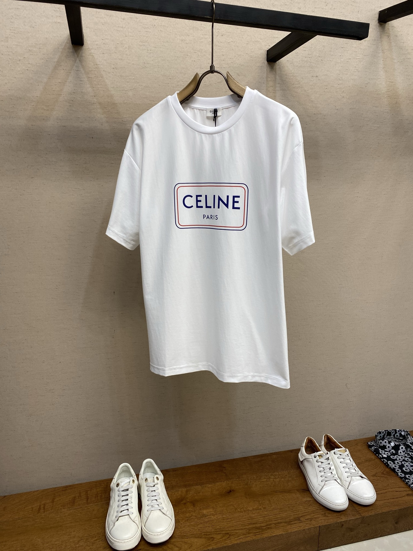 NO:655847,Celine blue frame printed round neck short sleeves, available in gray and white colors, originally purchased for 100; pure cotton fabric, CE classic printing, round neck loose fit, dropped shoulder design, collar decorated with ribbed trimming, horizontal cutting, full set of accessories #cotton jersey fabric  The main body is made of 24S special compact cotton to create a plain knitted fabric with a weight of g. The high count combed cotton yarn eliminates most of the short hairiness through the compact spinning process, making the yarn smoother and stronger. The woven fabric structure is extremely dense, flat and soft, with excellent anti-pilling ability and durability, while retaining the natural advantages of pure cotton being breathable and skin-friendly. The neckline is made of 32S 1x1 rib.  The weight is 300g, and the finer yarn count creates a more delicate and tight thread, which provides better elasticity and deformation resistance than ordinary ribs, ensuring that the neckline can still remain crisp after being put on and taken off many times. # CE classic powder printing  Silicone oil slurry printing is a printing process that is mixed with silicone oil and special slurry. Its characteristic is that it can form a matte and slightly astringent unique coating texture on the fabric. The printed area presents a soft matte effect, with moderate color saturation and a slight texture, which is in sharp contrast to common glossy offset printing.  In terms of hand feel, the printed area feels smooth with a slight pinkish resistance, similar to fine suede or chalk gray texture, without obvious filmy or hardening phenomena. Due to the addition of silicone oil, the pattern area maintains three-dimensionality while having excellent flexibility and crack resistance. It is not easy to crack after repeated rubbing, and its breathability is better than traditional thick paste printing, achieving a balance between decoration and wearing comfort. # Round neck, loose shoulder style  The fabric texture is cut horizontally. Horizontal cutting can make the body naturally adapt to the changes in body circumference. The horizontal texture will change the drape direction of the fabric under the action of gravity, forming natural vertical arc folds. It will produce a gentle wrapping feeling on the chest, abdomen and other parts, making it less restrictive when moving. It is especially suitable for slim or slightly elastic styles.  The core of the craftsmanship of the wide version of the round neck dropped shoulder T-shirt lies in the three-dimensional tailoring that breaks through the traditional shoulder line positioning. Its version creates a lazy and relaxed silhouette by greatly reducing the shoulder line point and increasing the looseness of the bust and sleeves. Although the neckline is a classic round neck, the collar size will be expanded accordingly to adapt to the dropped shoulder structure, and high-elastic ribs are used to prevent deformation. Sizes XS-L,,celine,T-shirt,tees,t-shirt,alexander wang19860909Celine 蓝框印花圆领短袖 发售色系花灰、白色  原,100购买；纯棉质面料、CE经典印花、圆领宽松版型、落肩设计、衣领饰有罗纹修边、横向裁剪、全套辅料配备 # 棉质平纹针织面料 主体采用24S特纺紧密棉打造平纹针织面料,克重g.高支数的精梳棉纱通过紧密纺工艺消除了大部分短毛羽,使得纱线更光滑、强韧.织成的面料结构异常密实、平整且柔软,具有出色的抗起球能力和耐用性,同时保留了纯棉透气亲肤的天然优势. 领口则选用32S 1x1罗纹 克重300g,更细的纱支编织出更细腻紧密的螺纹,提供了优于普通罗纹的回弹性与抗变形能力,确保领口历经多次穿脱后仍能保持挺括. # CE经典粉浆印花 硅油粉浆印花是一种通过硅油与特制粉浆混合调制的印花工艺,其特点在于能在面料上形成哑光微涩的独特涂层质感.印花区域呈现柔和雾面效果,色彩饱和度适中且带有微弱肌理感,与常见的光泽胶印形成鲜明对比. 手感方面,印花部位触感顺滑中带有些许粉糯阻力,类似细腻的绒面革或粉笔灰质地,无明显胶膜感或硬化现象.由于硅油的加入,图案区域在保持立体度的同时具备优异柔韧性和抗裂纹性能,反复揉搓不易开裂,且透气性优于传统厚浆印花,实现了装饰性与穿着舒适度的平衡. # 圆领宽松落肩版型 面料纹路为横向裁剪,横裁能使衣身自然顺应身体围度变化,横向纹路会改变重力作用下布料的垂坠方向,形成纵向的自然弧线褶皱.在胸、腹等部位产生轻柔的包裹感,活动时更少束缚,尤其适合修身或微弹款式. 宽大版型圆领落肩T恤的工艺核心在于突破传统肩线定位的立体剪裁.其版型通过大幅降低肩线落点与增加胸围、袖宽松量,营造出慵懒松弛的轮廓.领口虽为经典圆领,但会相应扩大领围尺寸以适应落肩结构,并采用高弹罗纹防止变形. 尺码XS-L,,celine,T-shirt,tees，t-shirt,alexander wang,Men's clothing