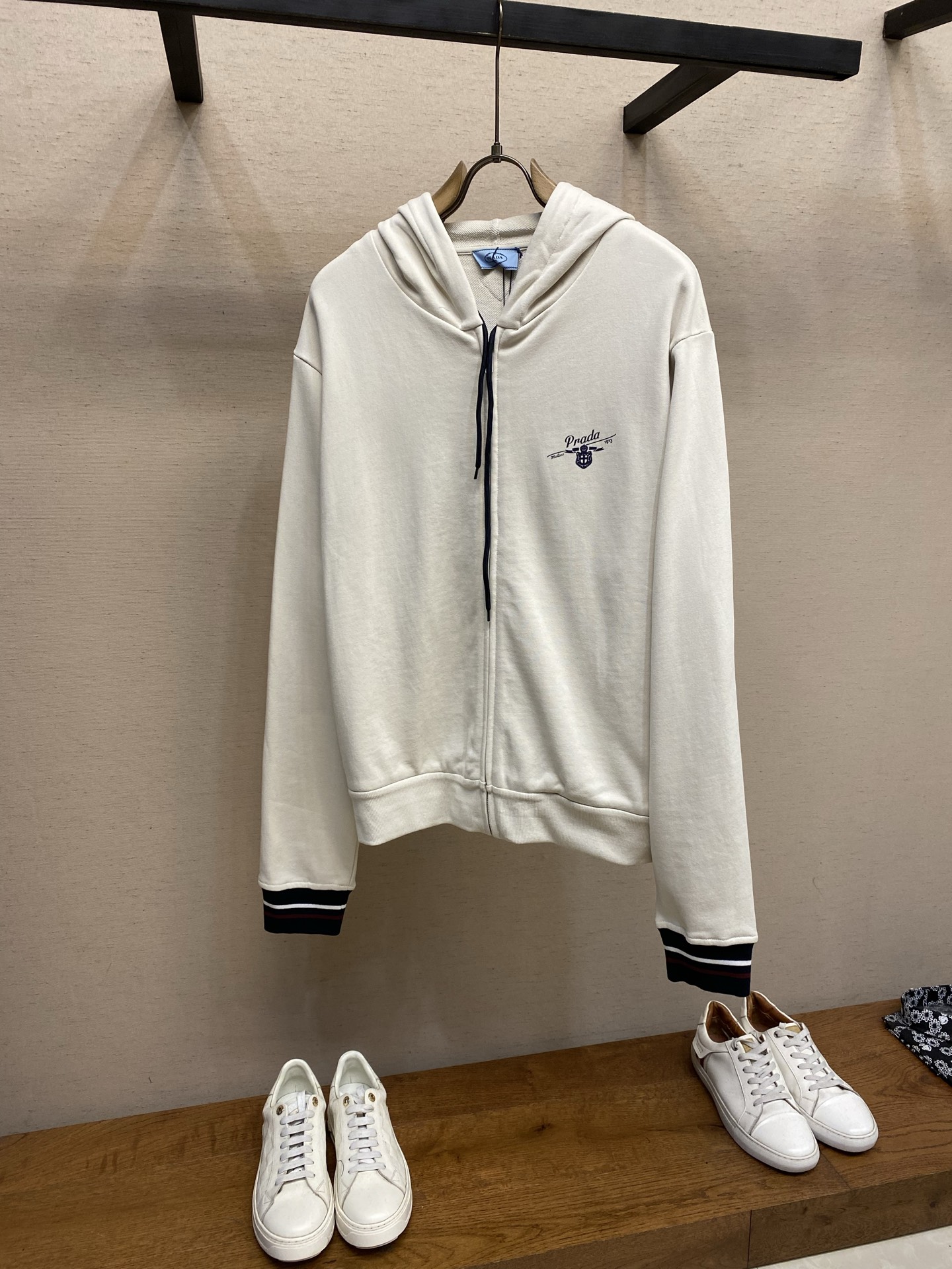 NO:728096,Prada supports after-sales college zipper hooded jacket. Original purchase, 200; pure cotton fish scale base fabric, elastic glue printing process, access control zipper opening and closing, jacquard flat machine cuffs, drawstring elastic design, full set of accessories # pure cotton fish scale base fabric  It adopts a 32-count single yarn top + 16-count yarn bottom sweatshirt fabric structure, with a weight of 320g/㎡; the matching 21-count 1x1 rib, a weight of 380g/㎡. It is used for the collar, cuffs and hem, providing good elasticity and closing shaping effects, ensuring wind resistance and neatness. In the middle of the body  A heavyweight and balanced fabric, the 32-count single yarn provides a delicate and smooth outer surface; the 16-count yarn bottom is raised to form a soft and warm fleece layer on the inside. The overall fabric is lighter and more flexible than traditional heavy sweaters, making it suitable for creating a jacket that combines warmth with ease of movement.  # Environmentally friendly elastic glue printing with retro effect  The Qianfu printing pattern adopts an environmentally friendly elastic glue printing process. The special environmentally friendly elastic glue is printed on the fabric through a screen and then solidified at high temperature. Its characteristics and functions are that the glue has good elasticity and can stretch with the fabric without cracking. It can present a matte or slightly glossy coating effect, and can achieve a retro look through old-fashioned color matching or processing. The touch is relatively soft and has no obvious hardened glue feel, ensuring the comfort of wearing. This kind of printing is durable and full of color, suitable for expressing eye-catching iconic patterns. #  Pattern design details  The square silhouette of the classic sports zipper hoodie is biased towards a loose, boxy modern sports style. The shoulder line has a dropped shoulder effect, and the body is H-shaped to create a retro, casual and neutral silhouette. The hood style and placket zipper are classic functional designs, providing protection and convenience for putting on and taking off. The drawstring design adopts a hidden dual-channel structure, and the rope body is wrapped with a custom webbing to avoid curling. The overall design aims to integrate the functional sense of sportswear, the sentiment of retro printing, and the modern fashion sense of loose silhouette.  Sizes XS-L,,prada,hoodie,sweatshirts,jackets & coats,hats,19860909Prada 支持年后售后学院拉链连帽外套 原,200购买；纯棉鱼鳞底面料、弹力胶浆印花工艺、门禁拉链开合、提花扁机袖口、抽绳松紧设计、全套辅料配备 # 纯棉鱼鳞底面料 采用32支单纱面+16支纱底的卫衣面料结构,克重为320g/㎡；搭配的21支1x1罗纹,克重为380g/㎡.用于领口、袖口和下摆,提供了良好的弹性和收口定型效果,确保防风且利落.衣身中重磅且注重平衡感的面料,32支单纱提供了细腻、平滑的外表面；16支纱底经过起绒处理,在内侧形成柔软温暖的绒毛层.整体面料比传统重磅卫衣更显轻盈灵活,适合打造兼具保暖性与活动便利性的外套. # 复古效果的环保弹力胶浆印花 前福印花图案采用环保弹力胶浆印花工艺,将特制的环保弹力浆料通过网版印刷在面料上,再经高温固化.其特点与作用在于浆料弹性好,可随面料拉伸不开裂；能呈现哑光或微光泽的涂层效果,通过做旧调色或工艺处理实现复古视觉；触感相对柔软,无明显硬化胶块感,保证了穿着的舒适度.这种印花耐用且色彩饱满,适合表达醒目的标志性图案. # 版型设计细节 经典运动格的拉链连帽衫方形轮廓,其剪裁偏向宽松、箱型的现代运动风格,肩线呈落肩效果,衣身呈H型营造复古、休闲且中性的廓形.帽子款式和门襟拉链是经典的功能性设计,提供防护和穿脱便利；抽绳设计采用隐藏式双通道结构,绳体包裹定制织带避免卷曲.整体设计旨在融合运动服的机能感、复古印花的情怀以及宽松廓形的现代时尚感. 尺码XS-L,,prada,hoodie,sweatshirts,jackets & coats,hats,,Men's clothing