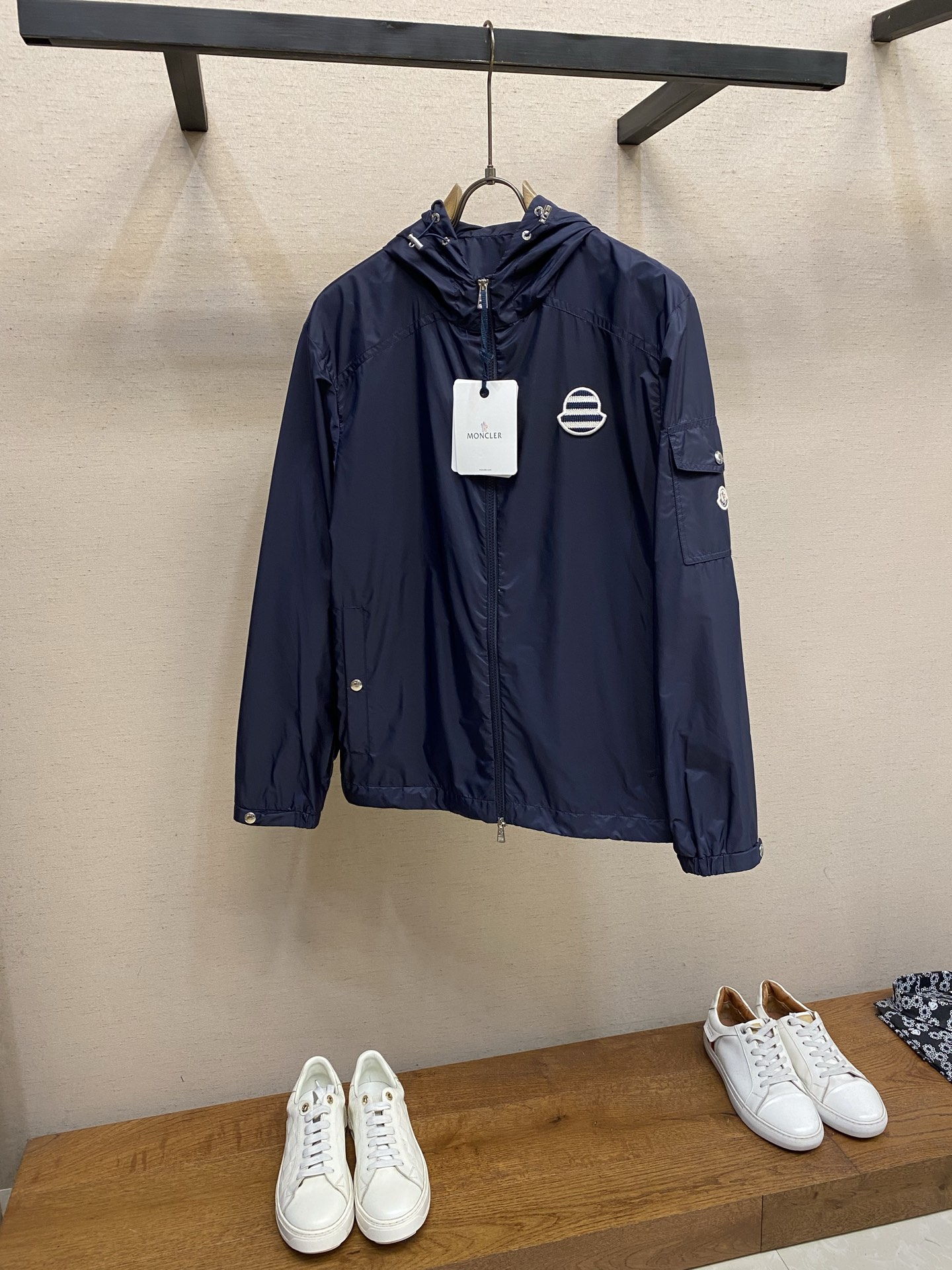 NO:834452,Moncler, hooded sun protection jacket, fabric selection, selects high-density nylon fabric. High-density nylon has natural physical sun protection properties. The fabric has a tight texture, which can effectively block direct ultraviolet rays and reduce the damage of the sun to the skin. It can be worn in summer without being stuffy. After lightweight processing, the weight on the upper body is greatly reduced. At the same time, nylon has excellent breathable and moisture-conducting properties. The micro-breathable structure on the surface can quickly discharge moisture from the body surface, making it less likely to stick to the body after sweating.  Details Customized metal snaps Side pockets, cuffs, and body are all made of brand-customized metal snaps with the brand logo engraved on the surface. They are smooth to press and not stuck, and are firm and not easy to fall off. They still maintain a bright texture after repeated opening and closing, and are not easy to oxidize and rust. The two-way zipper main zipper is a two-way custom metal zipper. The zipper head is engraved with a letter embossed logo. The zipper pulls smoothly without getting stuck, and is not easy to get stuck or break. The zipper teeth are polished and have smooth edges without burrs.  Metal rope buckle + air eye The drawstrings on the brim and hem are equipped with metal rope buckles and air eyes. The surface of the rope buckle is smooth and round, and can be pulled out smoothly. The tightness can be adjusted freely to cope with different wind conditions. The edge of the air eye is reinforced, making it difficult to scratch the fabric and providing maximum durability. Multi-layer composite embroidery process  A high-density computerized embroidery machine is used to fully embroider the main body stripes. High-fastness blue and white embroidery threads are used, and high-density filling embroidery is performed according to the preset twill path. By controlling the density and direction of the stitches, the three-dimensional sense and texture of the stripes are restored; the stitches are even and dense, with no skipping or missing stitches, making the transition between blue and white stripes clear and smooth.  The color is full and bright, and it is not easy to fade. After the main stripe embroidery is completed, a circle of overlock embroidery is performed along the outer contour of the embroidery seal, and the edge of the embroidery seal is wrapped with tight stitches. This can not only strengthen the structure of the embroidery seal and prevent the edges from going off-line and unraveling, but also outline a round and smooth outline, making the overall embroidery seal more refined and three-dimensional.  Sizes S-XL,,jackets & coats,hats,19860909Moncler,连帽防晒夹克 面料选择 甄选高密锦纶面料,高密锦纶自带天然的物理防晒属性,面料织构紧密,能有效阻隔紫外线直射,减少阳光对皮肤的伤害,夏天穿既能遮阳又不闷热,经过轻量化处理之后,上身负重感大大降低,同时锦纶自带优异的透气导湿性能,表面的微透气结构能快速排出体表湿气,出汗后不易闷汗黏身. 细节 定制金属按扣侧袋、袖口、衣身均采用品牌定制金属按扣,表面刻有品牌标识,按压顺滑不卡顿,牢固不易脱落,反复开合依旧保持光亮质感,不易氧化生锈. 双向拉链主拉链采用双向定制金属拉链,拉链头刻有字母浮雕标识,拉合顺滑不卡顿,不易卡齿、不易断裂；拉链齿经过抛光处理,边缘光滑无毛刺.  金属绳扣+气眼帽檐、下摆的抽绳搭配金属绳扣与气眼,绳扣表面光滑圆润,抽拉顺滑,可自由调节松紧,应对不同风势；气眼边缘加固处理,不易刮破面料,耐用性拉满. 多层复合刺绣工艺 采用高密电脑绣花机进行主体条纹的满绣制作,选用高牢度蓝白绣线,按照预设的斜纹路径进行高密度填充刺绣,通过控制针脚密度与方向,还原条纹的立体感与纹理感；针脚均匀细密,无跳线、无漏针,让蓝白条纹过渡清晰利落,色彩饱满鲜亮,不易褪色.主体条纹刺绣完成后,沿绣章外轮廓进行一圈包边锁绣,以紧密的针脚包裹住绣章边缘,既能加固绣章结构,防止边缘脱线、散边,又能勾勒出圆润流畅的轮廓,让绣章整体更具精致感与立体感. 尺码S-XL,,jackets & coats,hats,,Men's clothing
