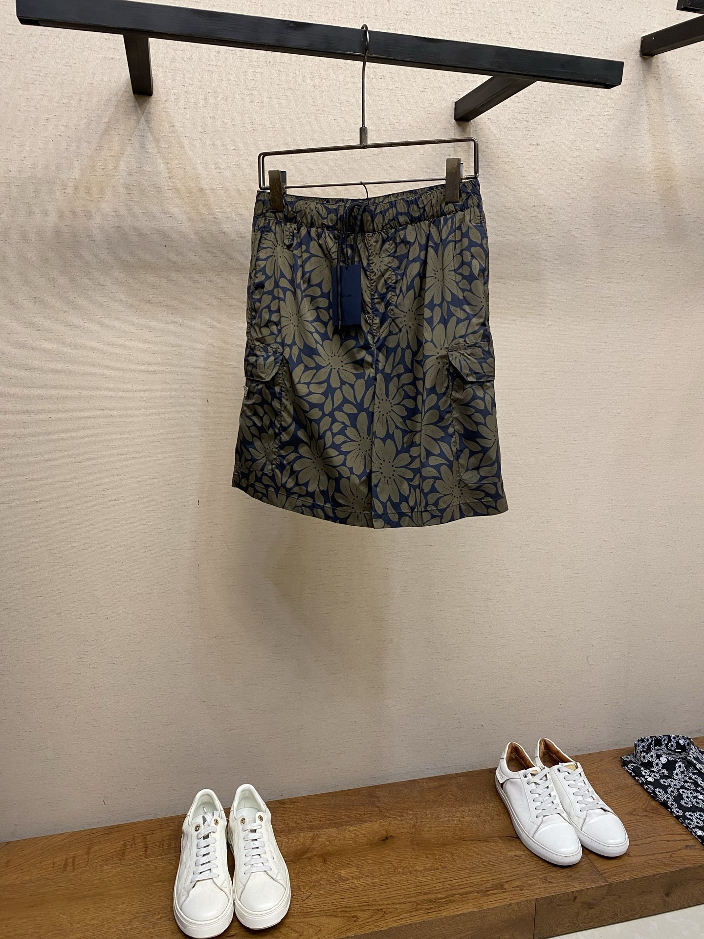 NO:915277,Prada, flower digitally printed nylon shorts. Fabric selection: Made of high-density nylon woven fabric, which has a crisp and drapey feel, is not easy to wrinkle and deform, is light in weight, has zero binding on the upper body, and will not sweat for a long time. After the surface is treated with water repellent, it is not easy to get wet with daily splashing of water, and minor stains can be wiped directly with clean water. Customized flower digital printing  Using environmentally friendly reactive digital printing technology, the large flower pattern is restored on the fabric at a ratio of 1:1. The color transition is natural and delicate, with clear gray-blue and black contrasting layers. There are no sharp jagged edges on the pattern edges, restoring the relaxed texture of hand-painted flowers. At the same time, through the high-temperature color fixation process, the printing layer is deeply integrated with the fabric fibers. Repeated machine washing is not prone to fading, cracking, and warping problems, and it remains as bright as new after long-term wear. Details  The lining is made of high-elastic breathable mesh. The mesh structure can quickly wick away moisture and sweat, preventing the stickiness of the fabric after sweating. It has a built-in 'air circulation channel' to keep you fresh and not stuffy even in hot weather. Sewing details 1: Before sewing, carefully check the floral print pattern on the bag piece and the trousers body to ensure that the pattern is restored at the splicing point to avoid pattern dislocation and faults, which will affect the overall aesthetics.  2. The two corners of the bottom of the bag are 'reinforced with dates' and the bartack length is 0.6cm to prevent the bottom of the bag from cracking due to the pulling of heavy objects and increase the service life. Sizes S-XL,, prada, shorts,19860909Prada,,花卉数码印花尼龙短裤 面料选择 选用高密尼龙梭织面料,自带挺括垂坠感,不易起皱变形,同时克重轻盈,上身后零束缚,久穿不闷汗.表面经过防泼水处理之后,日常溅水、都不易打湿面料,轻微污渍可直接用清水擦拭打理. 定制花卉数码印花 采用环保活性数码印花技术,将大花卉图案1:1还原在面料上.色彩过渡自然细腻,灰蓝色和黑色的撞色层次分明,图案边缘无生硬锯齿,还原手绘花卉的松弛质感.同时通过高温固色工艺,印花层与面料纤维深度结合,反复机洗也不易出现掉色、开裂、起翘的问题,久穿依旧鲜亮如新. 细节 内衬采用高弹透气网布,网眼结构能快速导湿排汗,避免出汗后面料贴肤的黏腻感,自带“空气流通通道”,闷热天气也能保持清爽不闷档. 缝纫细节 1:车缝前严谨核对袋片与裤身的花卉印花图案,确保拼接处的图案还原,避免出现图案错位、断层,影响整体美观度. 2.袋底两角做“打枣加固”,套结长0.6cm,防止重物拉扯导致袋底开裂,增加使用寿命. 尺码S-XL,,prada,shorts,,Men's clothing