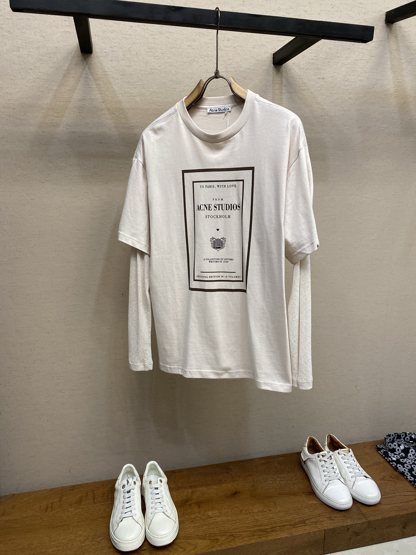 NO:838918,P, Acne Studios letter collection fake two-piece long sleeves. Original purchase; soft cotton jersey fabric, the fabric has a retro texture, fake two-piece structural design, seasonal graphic print on the chest, ribbed cuffs, round neck T-shirt, casual fit, full set of accessories #Soft cotton jersey fabric  The main body fabric is 12-count fine cotton plain weave, 230g/m; the matching rib uses 32-count double yarn, 350g/m. 12-count is a coarse yarn count, which means that the yarn is thicker and has a low twist. After being woven into plain weave, it will form an obvious slub feel or irregular texture. This kind of  The fabric gives up the smoothness and delicacy of combed cotton, and deliberately retains a dry feel and slightly loose structure similar to a retro distressed T-shirt. The weight of the fabric ensures that this rough texture will not collapse, and can independently support the loose silhouette. The upper body will have a crisp paper feel and excellent breathability.  The sleeves are made of polyester ribbing. Thorough heterogeneous splicing is used here. The body is made of soft pure cotton, but the sleeves are made of functional chemical fiber. Polyester ribbing has natural elastic recovery ability and drape, which allows the sleeve shape to rebound quickly even after strenuous activities, without causing bulges that are easy to appear on cotton cuffs. # The front chest is decorated with the seasonal letter collection pattern print  The seasonal pattern on the front chest adopts a penetration printing process. Through special additives and high temperature and high pressure conditions, the dye molecules are completely dissolved and penetrated into the interior of the cotton fiber, and are covalently bonded with the fiber. For fabrics with uneven surface texture such as 12-count roving, penetration printing shows great advantages and is evenly distributed along the fiber texture.  The most notable feature of the completed printing is that it has zero hand feel and cannot touch the border of the pattern. The thickness and softness of the fabric in the printed area and the blank area are exactly the same, maintaining the original dry texture of roving cotton. # Fake two-piece structure casual version  The silhouette is defined as a casual neutral silhouette, with length reaching the hips. This is a typical oversize silhouette. The hip-length design does not wrap the hips softly, forming a vertical blouse feel. Combined with the round neck design, this length-to-width ratio visually elongates the upper body line and is suitable for layering. In order to balance the dragging feeling brought by the long body, the ribbing or hemming process of the hem must be extremely fine to reduce the heavy feeling of fabric accumulation. Sizes XS-L,,acne  studios,dior,versace,tees,t-shirt,19860909P,Acne Studios 信件合集假两件长袖 原购买；柔软棉质平纹针织面料、面料具有复古质感、假两件结构设计、前胸饰有当季图案印花、罗纹袖口、圆领T恤、休闲版型、全套辅料配备 # 柔软棉质平纹针织面料 主身面料选用的是12支精棉平纹,230g/m；搭配罗纹采用了32支双纱,350g/m.12支属于粗纱支,这意味着纱线较粗且捻度较低,织成平纹布后会形成明显的竹节感或不规则肌理.这种面料放弃了精梳棉的光滑细腻,刻意保留了一种类似复古做旧T恤的干爽手感和微疏松结构.面料克重确保了这种粗犷肌理不会垮塌,能独立支撑起宽松的廓形,上身会有一种挺括的纸张感,透气性极佳. 衣袖采用了涤纶罗纹.这里运用了彻底的异质拼接衣身是柔软的纯棉,袖子却是功能性化纤.涤纶罗纹具有天然的弹性恢复能力和垂坠感,这使得袖型即使经过剧烈活动也能迅速回弹,不产生棉质袖口易出现的鼓包. # 前胸饰有当季信件合集图案印花 前胸的当季图案采用了渗透印花工艺,通过特殊的助剂和高温高压条件,使染料分子完全溶解并渗入棉纤维的内部,与纤维发生共价键结合.对于12支粗纱这种表面肌理凹凸不平的面料,渗透印花展现了极大的优势,顺着纤维纹理均匀分布. 完成后的印花最显著的特点是零手感,摸不到图案的边界,印花区域和空白区域的面料厚度、柔软度完全一致,保持了粗纱棉原始的干爽肌理. # 假两件结构休闲版型 版型定义为休闲中性版型,衣长及臀.这是一个典型的Oversize轮廓.长及臀部的设计不会软塌地包裹臀部,形成一个垂直的罩衫感.配合圆领设计,这种长宽比例在视觉上拉长了上半身线条,适合叠穿.为了平衡长衣身带来的拖沓感,下摆的罗纹或折边工艺必须做得极细,以减少面料堆积的厚重感. 尺码XS-L,,acne studios,dior,versace,tees，t-shirt,,Men's clothing