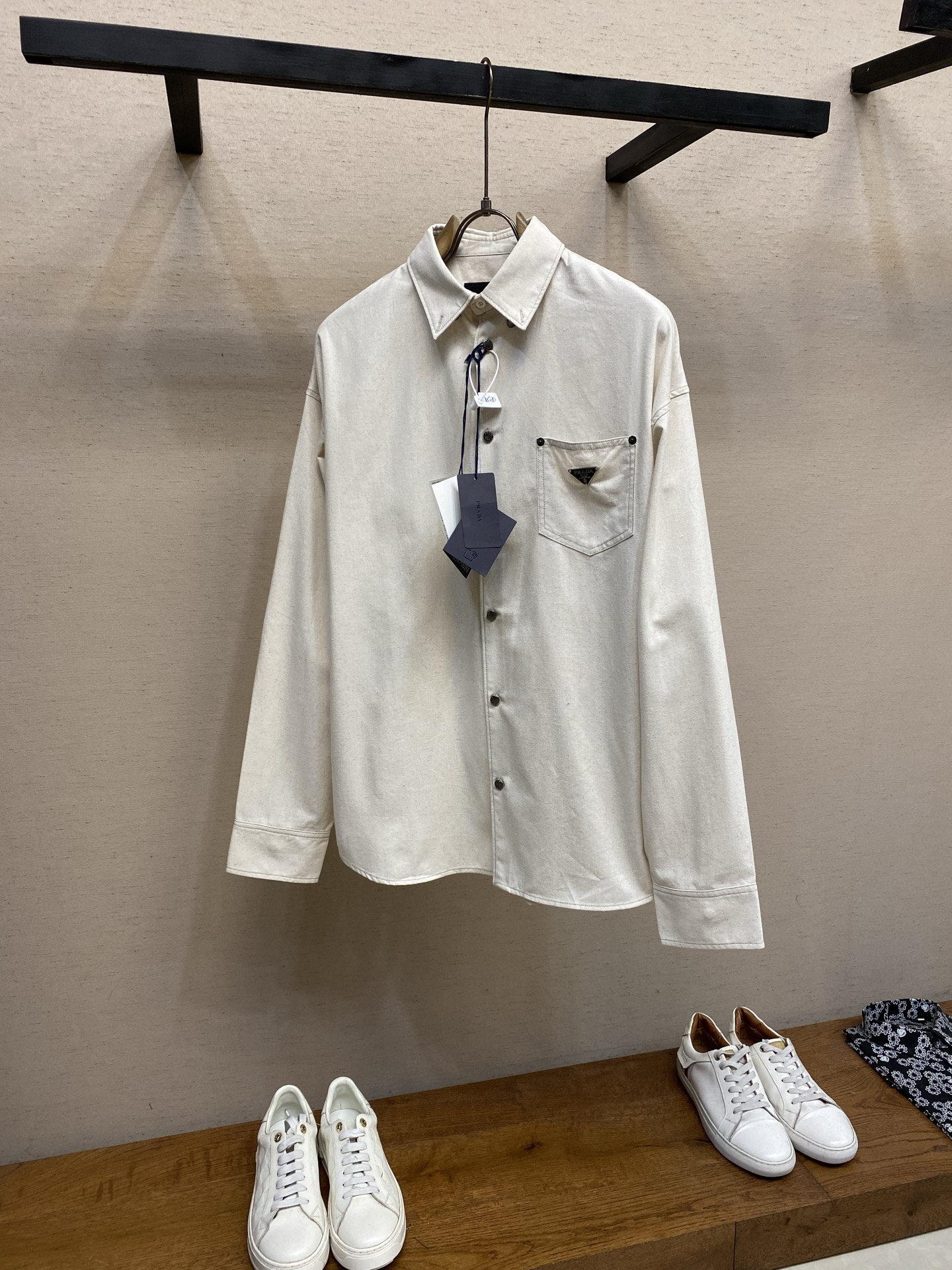NO:844344,Prada solid color single-breasted triangle logo long-sleeved shirt  This Prada shirt is made of selected corduroy fabric, which is soft and delicate to the touch, with a crisp texture and comfortable skin-friendly feel. The placket adopts precision sewing technology and is matched with metal buttons of the same color, with exquisite and durable details. The triangle logo on the left chest adopts three-dimensional embroidery technology, with fine stitching and full brand recognition. The shoulders are cut with dropped shoulders, and precise dart processing is used to ensure a loose fit while taking into account smooth lines; the cuffs are designed with a single button.  The fit can be adjusted to take into account practicality and style. The ready-made garments are pre-shrunk to effectively reduce the shrinkage after washing and ensure a stable version. The whole body adopts overlock sewing technology, and the inner wiring is smooth to improve wearing comfort. The weight is controlled at 470g, taking into account the warmth and lightness in autumn and winter. There is an error of 1-3cm in manual measurement, which is within the normal range. The overall wiring is straight and delicate, the fabric is comfortable and soft, and the color is consistent and without color difference.  It can be matched with the same style to create a fashionable look, and can be used in various occasions. Customized accessories, complete with three standards, same style for men and women!  Size S-XL,,prada,prada,shirts,19860909Prada 纯色单排扣三角标长袖衬衫 这款普拉达衬衫采用精选灯芯绒面料,触感柔软细腻,兼具挺括质感与舒适亲肤性.门襟采用精密车缝工艺,搭配同色系金属纽扣,细节精致耐用；左胸三角徽标采用立体刺绣工艺,针脚细密,品牌辨识度拉满.肩部采用落肩剪裁,通过精准的省道处理,保证宽松版型的同时兼顾线条流畅度；袖口采用单扣设计,可调节贴合度,兼顾实用性与造型感.成衣经过预缩水处理,有效降低洗涤后的缩水率,确保版型稳定.整体采用无锁边包缝工艺,内里走线平整,提升穿着舒适度；克重控制在470g,兼顾秋冬保暖性与轻盈感,手工测量存在1-3cm误差,属于正常范围.整体走线平直细腻,面料舒适柔软,颜色一致无色差 能与同款搭配营造时尚造型,驾驭各种场合,定制辅料,三标齐全,男女同款！ 尺码S-XL,,prada,prada,shirts,,Men's clothing