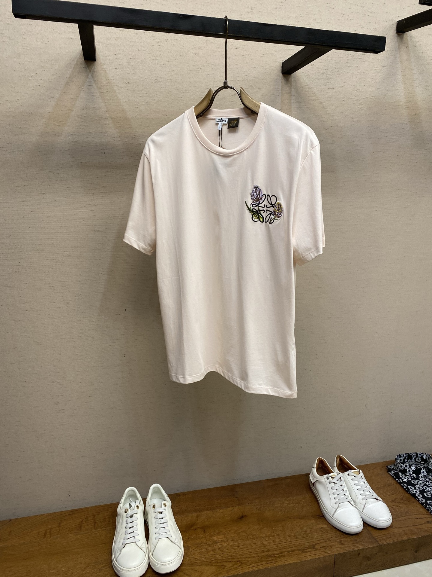 NO:844325,Loewe, Artichoke Anagram embroidered T-shirt. Fabric: 24-count special woven compact cotton / 285G. Rib: 32-count 1×1 rib / 340G This short-sleeved shirt is made of 24-count special-spun compact cotton, which is a medium-thick knitted fabric that is both stiff and comfortable. The compact spinning technology makes the fibers arranged parallel, hairiness is significantly reduced, and the surface is smooth and smooth. After shaping, the fabric has both stiffness and softness, and a moderate drape, which provides a smooth and stable base fabric for subsequent two-color embroidery. The artichoke Anagram embroidery on the front adopts tatami embroidery technology. Through high-density and regularly arranged parallel stitches, a large area of flat filling or exquisite edge outline is achieved. The stitches are closely arranged in a fixed direction to form a texture similar to that of a tatami mat. The embroidery surface is flat and dense, has a delicate gloss and solid touch, is wear-resistant and has a strong three-dimensional feel, giving the artichoke pattern a delicate and textured visual effect. Size XS-L,,loewe,T-shirt,tees,t-shirt,19860909Loewe,洋蓟Anagram刺绣T恤 面料24支特纺紧密棉 / 285G 罗纹32支1×1罗纹 / 340G 这款短袖选用24支特纺紧密棉,属于兼具挺括与舒适的中厚型针织面料.紧密纺技术使纤维排列平行、毛羽显著减少,表面光洁平滑.定形后的面料兼具挺括性与柔软度,垂坠感适中,为后续的双色刺绣提供了平整稳定的底布基础. 正面洋蓟Anagram刺绣采用榻榻米绣工艺.通过高密度、规律性排列的平行针迹,实现大面积的平整填充或精致边缘勾勒.针迹按固定方向紧密排列,形成类似榻榻米草席的纹理,绣面平整致密,具有细腻的光泽感和扎实的触感,耐磨且立体感强,使洋蓟图案呈现出精致而富有质感的视觉效果. 尺码XS-L,,loewe,T-shirt,tees，t-shirt,,Men's clothing