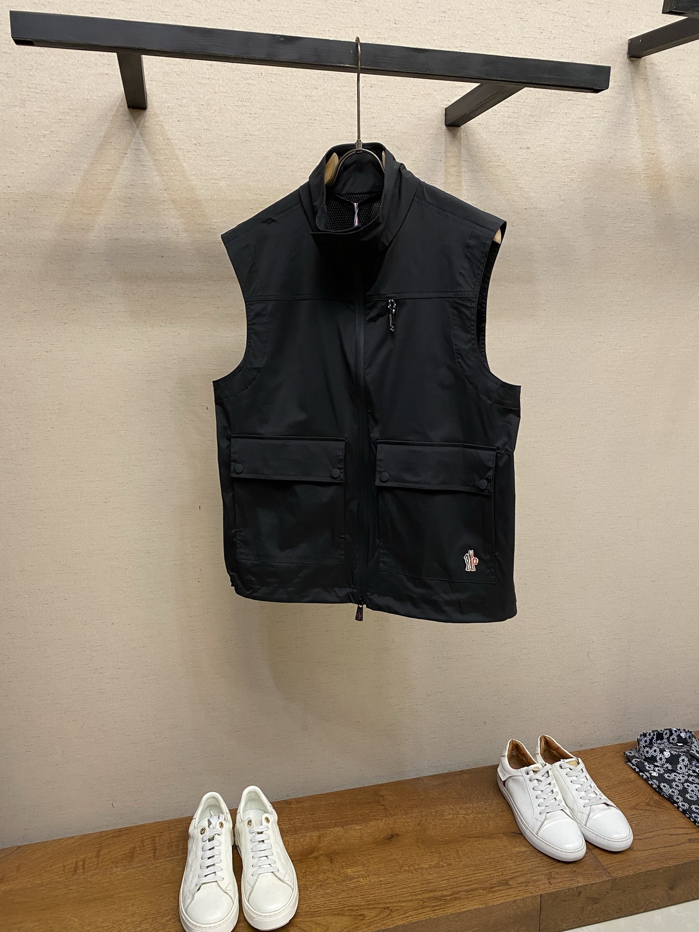 NO:915280,Moncler, reflective logo outdoor vest fabric selection uses nylon as the main fabric, which has high-strength tear-resistant and abrasion-resistant properties, and the surface has been specially treated to be wind- and water-repellent. With the inner layer coating, it achieves 'wind-proof and water-proof' protection while retaining the lightweight nature of the fabric. It does not feel heavy and restrictive when worn alone. Mesh lining  Made of nylon + spandex blended breathable mesh, with a small amount of spandex to add four-dimensional elasticity, it fits the lines of the shoulders and back without being tight, allowing unrestricted movement, and is not easily deformed or loose after stretching. The mesh texture has uniform gaps, smooth air circulation, and can quickly dissipate heat and moisture from the body surface. Laminating process  The film is combined with the fabric through hot-pressing lamination technology instead of ordinary glue, which avoids the problem of film peeling and blistering after long-term wear, while maintaining the softness of the fabric and not becoming stiff and hard due to the film. The printing process uses thermoset ink screen printing, and the printer deeply combines the ink with the fabric fibers through three scrapings. The printing has no glue feel, is not stiff, and is friction-resistant, and will not fall off easily due to daily wear and friction. The printing edges are sharp, there is no smudged burr, and the proportion of fonts and patterns is accurately restored.  Reflective logo: Through the reflective cloth punching process, the logo is regularly arranged on the triangular reflective mark with dozens of small holes, which improves functionality and strengthens recognition and aesthetics. Appearance details 1. The main zipper adopts a waterproof laminated zipper, the surface of the teeth is smooth, the slider has a brand logo, and the edge of the zipper is laminated to prevent rainwater from seeping through the gap of the zipper. At the same time, there is an anti-pinch design on the inside of the zipper to avoid jamming when closing.  2. The hem is equipped with a black and white webbing drawstring and is matched with a Moncler custom-made rope buckle. The end of the drawstring is fixed with a woven label. The rope buckle opens and closes smoothly and can quickly adjust the tightness of the hem to prevent the intrusion of cold wind. At the same time, the rope buckle has no unnecessary edges and corners to avoid scratching the fabric or skin. Sewing details: The inside of the stand-up collar is hemmed, and all seams are made of double-thread sewing technology. The stitches are even and fine, and the stress-bearing parts are additionally reinforced to improve the overall durability. Size S-XL,,19860909Moncler,,反光标识户外马甲  面料选择 采用锦纶主面料,其本身具备高强度抗撕裂、耐磨损特性,且表面经过特殊拒风拒水处理,配合内层覆膜,实现“风穿不透、水泼不进”的防护力,同时保留面料轻量化特质,成衣之后单穿无厚重束缚感. 网眼内衬 选用锦纶+氨纶混纺透气网眼,少量氨纶加持四维弹力,贴合肩背线条不紧绷,活动无拘束,拉伸后不易变形、不松垮.网眼肌理空隙均匀,空气循环通畅,快速疏导体表热气与湿气. 覆膜工艺 通过热压复合技术将薄膜与面料结合,而非普通胶水粘合,避免长期穿着后出现膜层脱落、起泡问题,同时保持面料的柔软度,不会因覆膜变得僵硬板结. 印花工艺 采用热固油墨丝网印花,印花师通过3次刮印使油墨与面料纤维深度结合,印花无胶感、不发硬,且具备耐摩擦特性,日常穿着摩擦不会轻易脱落.印花边缘锐利,无晕染毛边,字体与图案比例精准还原.  反光标识: 通过反光布冲孔工艺将Logo以数十个小孔规则排列呈现在三角形反光标之上,提升功能性的同时强化了辨识度和美观性.  外观细节 1.主拉链采用防水压胶拉链,链牙表面顺滑,拉头带有品牌标识,拉链边缘经过压胶处理,防止雨水从拉链缝隙渗入,同时拉链内侧设有防夹布设计,避免拉合时卡布.  2.下摆配备黑白相间的织带抽绳,搭配Moncler定制绳扣,抽绳末端固定织标,绳扣开合顺滑,可快速调节下摆松紧,防止冷风灌入,同时绳扣无多余棱角,避免刮伤面料或皮肤. 缝纫细节 立领内侧通过包边处理,所有接缝处采用双线车缝工艺,针脚均匀细密,受力部位额外做加固处理,提升整体耐用性. 尺码S-XL,,,Men's clothing