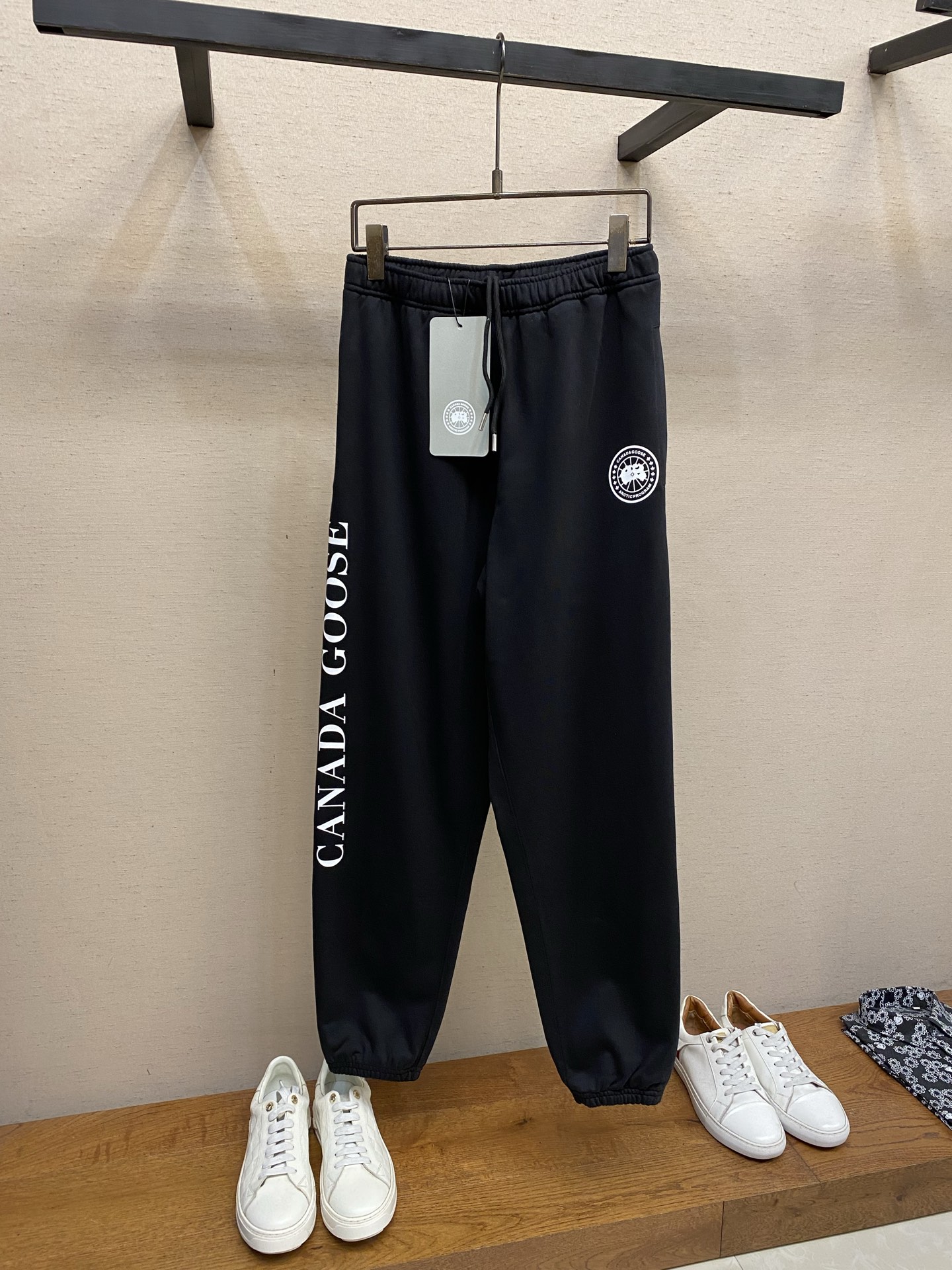 NO:849974,, Canada Goose Letter Pattern Printed Sweatpants Fabric Selection: Single-sided fish scale fabric woven with cotton as the base, with a smooth knitted surface on the front, and a three-dimensional terry surface formed by the floating knitting technology of the knitting machine to increase the fluffiness and delicate touch on the skin surface. The terry structure absorbs large amounts of water and evaporates quickly, and is not easy to loosen and deform after repeated washing. Printing process  The glue screen printing process is used to present two high-saturation patterns and letters. The background color is printed first and then the details are outlined. The scraper pressure is even and the scraping is done in three steps. The outlines of the map, maple leaves and letters are clearly layered, and the pattern is full and three-dimensional. After the scraping printing is completed, it goes through a high-temperature heat-setting drying process to lock the color and shape. The touch is smooth and not hard, does not rub the skin, and is not heavy. The printing and fabric are perfectly integrated, taking into account both aesthetics and durability, perfectly presenting the texture of the classic logo. Detail 1  The waistband is made of widened and high-elastic elastic, double-layer hemming and sewing, and multiple dense stitching reinforcements. The elasticity is even and does not tighten the waist, and it is not easy to loosen after long-term wear. It is equipped with a customized metal-tipped drawstring, with laser-engraved brand letters on the rope head. The metal texture is delicate and wear-resistant, and the drawstring is neatly routed. It can be pulled smoothly without lag. The waistline can be adjusted freely to suit various body shapes. Detail 2  The trouser hem is designed with full elasticity and double-needle overlocking. The stitching is fine and even, and the closing is tight and not loose. Detail 3: The side seams of the trouser body are made of double-thread overlocking technology, which is straight and neat, and the seams are firm and not easy to collapse and crack; the inside is fully hemmed, without excess raw edges. Size S-XL,,19860909,Canada加拿大鹅字母图案印花运动裤 面料选择 采用棉为基底编织而成的单面鱼鳞布面料,正面为平滑的针织面,触肤面通过针织机的浮线编织技术形成立体的毛圈,增加蓬松感, 同时触感细腻.毛圈结构吸水量大且蒸发快,多次洗涤不易松散变形. 印花工艺 采用胶浆丝网印花工艺,呈现两处高饱和度图案与字母,先印底色再勾勒细节,刮刀压力均匀,分3次刮印,地图、枫叶、字母轮廓层次分明,图案饱满立体.刮印完成之后再经过高温热固烘干工艺,锁色定型,触感平整不发硬,不硌肤、不厚重,印花与面料完美融合,兼顾美观度与耐穿性,完美呈现经典标识质感. 细节1 腰头采用加宽高弹松紧带,双层包边车缝,多道密集针脚加固,弹力均匀不勒腰,久穿不易松垮.搭配定制金属头抽绳,绳头做激光雕刻品牌字母,金属质感细腻耐磨,抽绳走线规整,抽拉顺滑不卡顿,可自由调节腰围,适配各种身形. 细节2 裤脚束口设计,罗纹弹力饱满,同样采用双针锁边车缝,针脚细密均匀,收口紧致不松垮. 细节3 裤身侧缝采用双线包缝工艺,走线笔直工整,锁边牢固不易崩线开裂；内里全部包边处理,无多余毛边线头. 尺码S-XL,,,Men's clothing
