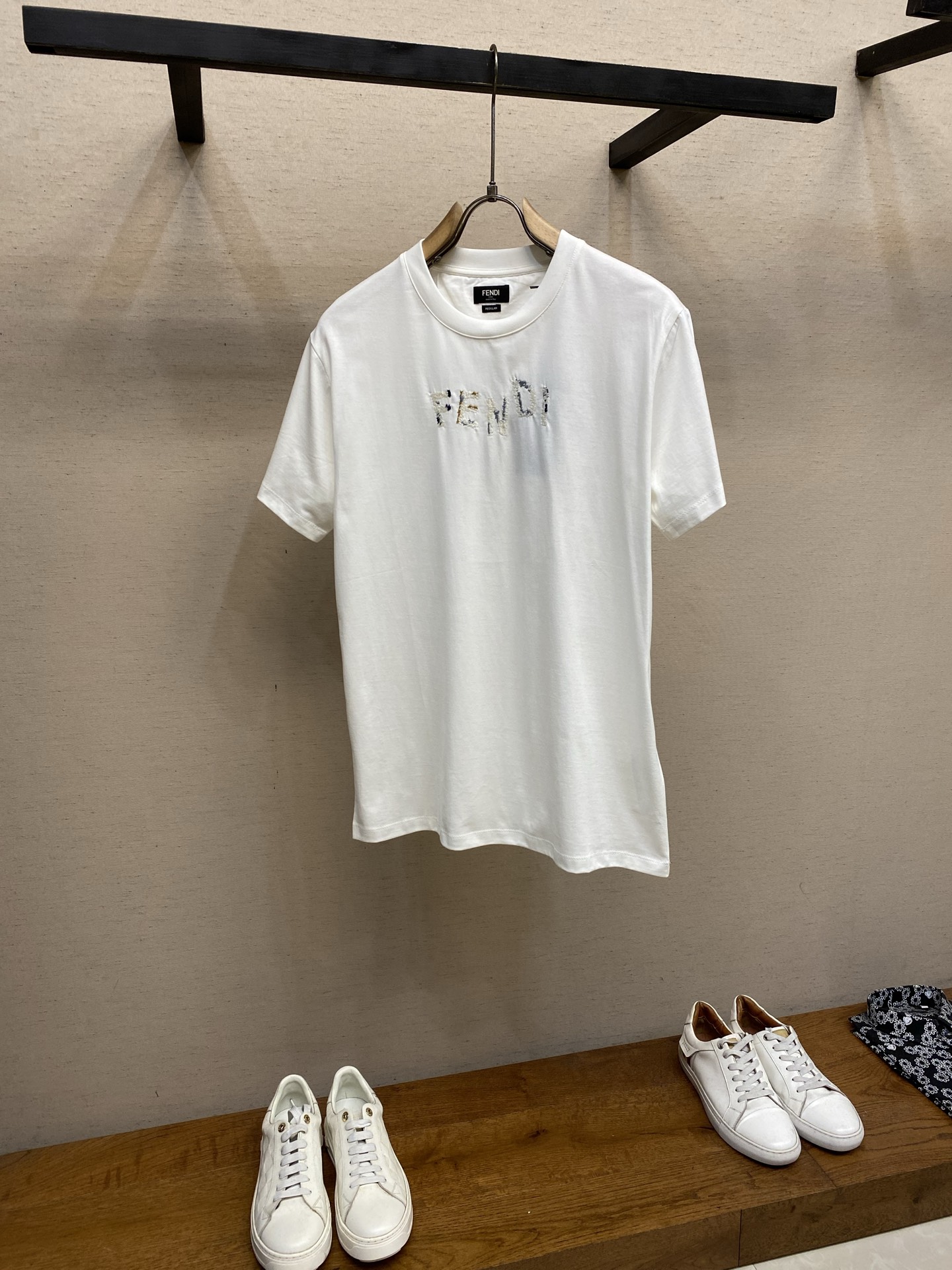 NO:849978,PFendi, miscellaneous yarn embroidered round neck short sleeves, available in navy blue and white. Original purchase; double yarn mercerized cotton fabric, embroidered logo of the same color on the chest, contrasting yarn details, slim fit short sleeves, round neck, full set of accessories # double yarn mercerized cotton fabric  50-count double-ply mercerized cotton, 165g/m, is used with 32-count double yarn, 300g/m ribbing. 50-count is a high-fine yarn count, and the yarn diameter is extremely fine; it also meets the smoothness standard of high-end shirts. The double-ply yarn is made of two single yarns and twisted into one yarn. This process  The technique simultaneously achieves the smoothness of thin counts and the strength of double strands, making the yarn both delicate and not easy to break. Mercerizing treatment changes the cotton fiber from a flat curled ribbon to a circular expanded shape, enlarging the cross-section and making the surface smoother; at the same time, the dye adsorption capacity is enhanced, and the color after dyeing is more saturated and brighter.  # The chest is decorated with same-color embroidery logo words. The same-color embroidery words on the chest are made using multi-color needle embroidery technology, and are matched with contrasting yarn details to form rich visual layers and tactile changes. The needle embroidery is derived from traditional hand embroidery techniques, and its effect is simulated by a multi-needle computer embroidery machine.  The embroidery traces on the front of the fabric formed by needle embroidery have a slight fluffy feel, which is soft to the touch rather than stiff; the needle tube of the needle is hollow, and the embroidery thread passes through it. The front shows a fluffy yarn arrangement, with a three-dimensional texture similar to tufting. During the embroidery process, the computer embroidery machine switches the embroidery thread contrasting yarns of different colors according to the plate positioning, visually forming jumping color nodes. It is distributed on different paragraphs of the same letter, forming a rich gradient of the same color. #  Slim Fit Short Sleeve Round Neck The short sleeves adopt a slim fit with a short sleeve round neck design. The shoulder width is almost equal to the natural shoulder width. It is cut with a straight shoulder, and the shoulder seam is precisely located at the acromion. The waist and hem are significantly narrowed, fitting the body curve but not tight. The sleeve shape is narrow and straight, the cuff width is close to the upper arm circumference, and the overall outline is clean and neat.  Because the surface of mercerized cotton is extremely smooth, the armhole arcs are processed with extremely fine seams and gentle seams to avoid fabric accumulation and bulging at the seams. The neckline is made of high-weight double-yarn ribbing with excellent elastic recovery rate to ensure that the neckline fits well without being stretched. Sizes XS-L,, fendi, shirts, T-shirt,19860909PFendi,杂纱绣圆领短袖 发售色系藏蓝、白色 原购买；双纱丝光纯棉材质面料、胸前饰有同色系刺绣标识字样、搭配撞色纱线细节、修身版型短袖圆领、全套辅料配备 # 双纱丝光纯棉材质面料 选用了50支双股丝光棉,165g/m,搭配32支双纱,300g/m的罗纹.50支属于高细纱支,纱线直径极细；更是达到了高级衬衫的光洁度标准.双股由两根单纱并捻成一根纱线,这一工艺同时实现了细支的柔滑与双股的强韧,使纱线既细腻又不易断裂.丝光处理将棉纤维由扁平卷曲带状变为圆形膨胀状,横截面扩大,表面更光滑；同时染料吸附能力增强,染色后色彩更饱和、更鲜艳. # 胸前饰有同色系刺绣标识字样 胸前饰有的同色系刺绣字样采用了多色插针刺绣工艺制作,并搭配撞色纱线细节,形成丰富的视觉层次和触感变化.插针刺绣源于传统手工刺绣技法,由多针位电脑刺绣机模拟其效果. 插针刺绣形成的面料正面绣迹具有轻微的蓬松绒毛感,触感柔软而非硬挺；插针的针管中空,绣线从中穿过.正面呈现出蓬松的纱线排列,具有类似簇绒的立体质感.电脑绣花机在刺绣过程中,对版定位切换不同颜色的绣线撞色纱线,在视觉上形成跳跃的色彩节点.在同一字母的不同段落上分布,形成层次丰富的同色系渐变. # 修身版型短袖圆领 短袖采用修身版型搭配短袖圆领设计.肩宽几乎等于自然肩宽,采用正肩剪裁,肩缝精准落在肩峰位置；腰部和下摆明显收窄,贴合身体曲线但不紧绷.袖型为窄条直筒,袖口宽度与大臂围接近,整体轮廓干净利落. 由于丝光棉表面极其光滑,袖笼弧线的处理采用极细的缝份与轻柔的止口,避免接缝处产生面料堆积鼓包.领口采用高克重双纱罗纹,弹性恢复率优异,确保领口贴合而不勒. 尺码XS-L,,fendi,shirts,T-shirt,,Men's clothing