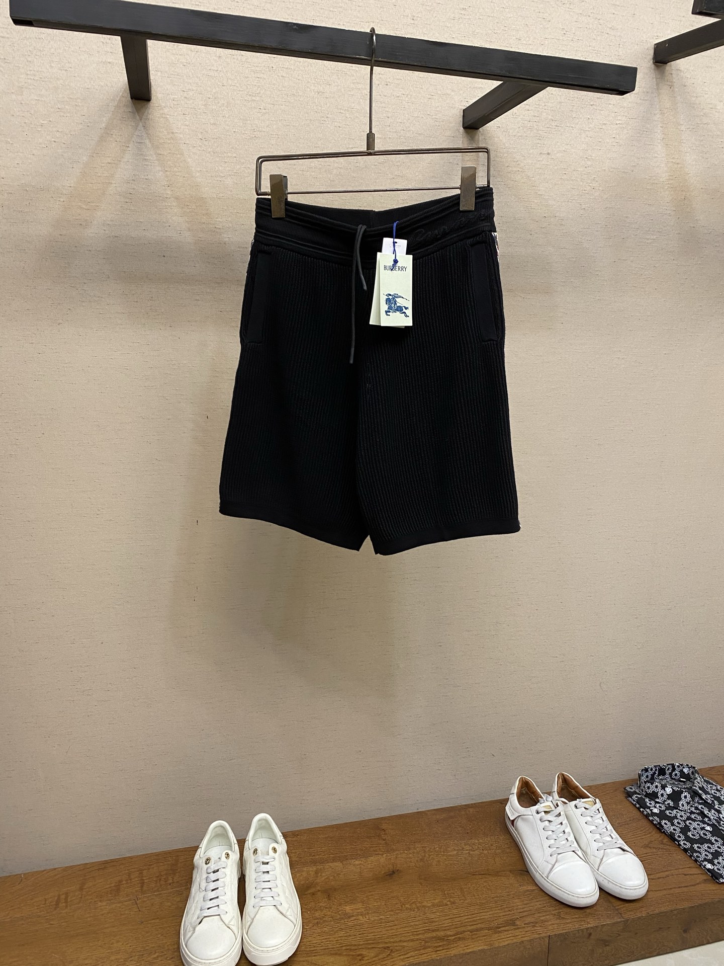 NO:930939,BBR, plaid decorative knitted shorts fabric weaving  The main body is woven with high-count lightweight cotton yarn, using the vertical pit rib knitting process. The yarn is plied and shaped, and is woven with a circular knitting machine to create a three-dimensional vertical grain texture. The special weaving method forms an air layer inside the fabric, which is soft and not heavy to the touch, taking into account both breathability and drape. The texture of the cloth surface is even and regular, and is not easy to deform and wrinkle. The pit strips remain clear and three-dimensional after multiple washes, making it comfortable and non-restrictive to wear close to the body. Details  The retro plaid knitted webbing is spliced on both sides of the trousers, using synchronous jacquard knitting technology. The plaid is woven simultaneously with multi-color yarns, with clean color boundaries and no halo jumpers. The webbing and trouser body panels are precisely sewn and spliced, and the lines are straight and firm. The classic plaid elements break the monotony of pure black fabrics, highlighting the recognition in simplicity. Jacquard technology  The waistband has a widened ribbed one-piece woven structure with a built-in cotton drawstring, and the rope ends are sealed to prevent loose threads. The waistband is integrated with cursive letter jacquard craftsmanship, and the yarns are woven in layers to form a slightly raised three-dimensional texture and a faint relief effect, which is smooth to the touch but rich in visual layers. Sizes S-XL,,shorts,19860909BBR,,格纹装饰针织短裤  面料织造 主体选用高支轻盈棉质纱线织造,采用竖向坑条罗纹针织工艺,纱线经过合股定型处理,经由大圆机一体织出立体竖纹肌理.特殊织法形成面料内部空气层,触感柔软不厚重,兼顾透气度与垂坠感；布面纹理均匀规整,不易变形起皱,多次水洗后坑条依旧清晰立体,贴身穿着舒适无束缚.  细节 裤身两侧拼接复古格纹针织织带,采用同步提花针织工艺,格纹由多色纱线同步织入,色彩边界干净利落,无晕色跳线.织带与裤身裁片精密车缝拼接,走线平直牢固,经典格纹元素打破纯黑面料单调感,简约中凸显辨识度.  提花工艺 腰头为加宽罗纹一体织结构,内置棉质抽绳,绳头做封胶处理不易散线.腰头处融入草书字母提花工艺,纱线分层织入形成微微凸起的立体纹路、若隐若现的浮雕效果,触感平滑却视觉层次丰富. 尺码S-XL,,shorts,,Men's clothing