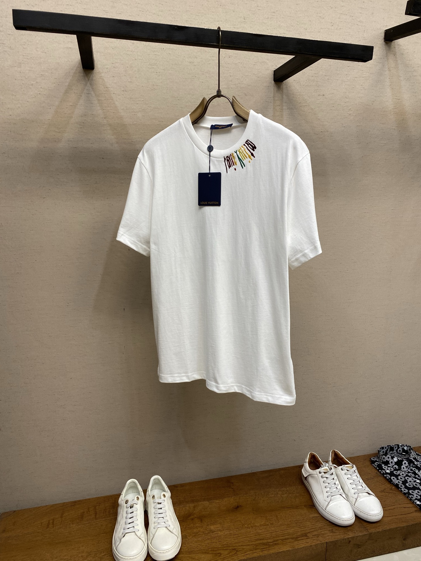 NO:947068,1V,, Team color-labeled round-neck short-sleeves, originally purchased from overseas; pure cotton round-neck short-sleeves, positioning pin embroidery technology, colorful environmentally friendly elastic glue printing, round-neck ribs, standard version, full set of accessories # Pure cotton plain fabric  It uses 15S special spinning compact cotton with a weight of 230g/m; with 32S1×1 ribbing on the neck, the weight is as high as 340g/m. Compact spinning technology can effectively eliminate yarn hairiness, making the yarn body smooth and even, giving the fabric surface a slightly matte high-end texture.  , and improves the anti-pilling performance. The medium weight of the fabric has both a drape feel and a flexible frame; it can naturally fit the body curve and maintain the outline. This high-density, high-weight rib has a tight structure, solid texture, excellent elasticity and resilience, and can firmly lock the collar.  # Positioning needle embroidery process Four-color wool and cotton thread needle embroidery is a composite embroidery process that combines multi-material yarns and three-dimensional stitching; the wool is responsible for constructing the main color and fluffy volume of the pattern, and the cotton thread is used to outline the fine outline and fix the underlying structure. The needle embroidery uses stitches with staggered lengths and changing directions to make yarns of different colors form natural color gradients and texture transitions on the surface of the fabric, and sharp edges are achieved through precise narrowing of cotton threads at the edges. #  Colorful and environmentally friendly elastic glue printing. Modern printers who use water-based polymer environmentally friendly slurry accurately transfer the special elastic glue to the fabric through a high-mesh screen. After curing at high temperature, a flexible and highly elastic printing film layer is formed. The printing effect presents a matte or semi-matte texture, saturated colors and strong coverage, with a soft and smooth touch without the feeling of film hardening, while maintaining the original breathability of the fabric. # Standard round neck version  The short sleeves adopt a standard round neck shape, with the shoulder line accurately falling on the acromion point. The body is straight-cut, with similar bust and hem circumferences, fitting but not tight. The sleeve shape is standard short sleeves, and the collar, cuffs and hem are finely closed, with a simple structure. The whole body is within the standard version frame, and through the stiff support of medium-thick fabrics, it presents a casual wearing experience with exquisite craftsmanship. Size XS-L,, T-shirt,198609091V,,团队彩标圆领短袖 原海外采购；纯棉质圆领短袖、定位插针刺绣工艺、彩色环保弹力胶浆印花、圆领罗纹、标准版型、全套辅料配备 # 纯棉质平纹面料 选用15S特纺紧密棉,克重为230g/m；搭配领口32S1×1罗纹,克重高达340g/m.紧密纺技术能有效消除纱线毛羽,使纱体光洁、条干均匀,这让面料表面呈现出微雾面的高级质感,并提升了抗起毛球性能.面料中克重,兼具了垂坠感与柔韧的骨架；能自然地贴合身体曲线,保持轮廓.这种高密度、高克重的罗纹结构紧密、质地扎实,具有极佳的弹力和回弹性,能牢牢锁住领圈. # 定位插针刺绣工艺 四色毛线加棉线插针绣是一种融合多材质纱线与立体针法的复合刺绣工艺；毛线负责构建图案的主体色彩与蓬松体积感,棉线则用于勾勒精细轮廓与固定底层结构.插针绣通过针脚长短交错、方向多变的针法,使不同颜色的纱线在面料表面形成自然的色彩渐变与肌理过渡,边缘处通过棉线的精密收针实现锐利边界. # 彩色环保弹力胶浆印花 采用水性高分子环保浆料的现代印花工,通过高目数丝网网版,将特制的弹力胶浆精准转印至面料,经高温固化后形成柔韧、高弹的印花膜层.印花效果呈现哑光或半哑光质感,色彩饱和且覆盖力强,触感柔软平滑无胶膜硬化感,同时保持面料原有的透气性. # 标准圆领版型 短袖采用标准圆领版型,肩线精准落在肩峰点,衣身呈直筒剪裁,胸围与下摆围度相近,合身而不紧身.袖型为标准短袖,领口、袖口与下摆均采用精细收口,结构简洁.整体在标准版型框架下,通过中厚面料的挺括支撑,呈现出兼具精致工艺的休闲感的穿着体验. 尺码XS-L,,T-shirt,,Men's clothing