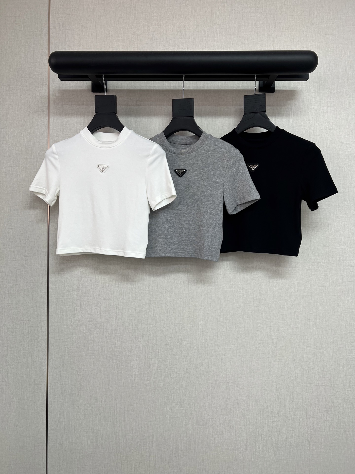NO:753915,High-quality PRADA 2026 spring and summer new P family tight-fitting T-shirt, short-sleeved high-elastic T-shirt, classic triangle logo decoration on the chest. This tight-fitting short-sleeved short T-shirt is a little expert in outlining the body shape. The neat tailoring adheres to the lines, the short-sleeved design is refreshing and neat, and the short length just exposes the waistline, quietly  Elongates the proportions of the lower body. It goes well with jeans and sports pants on a daily basis. It is easy to wear with a sense of vitality and neatness, and the movements are casual and energetic. Gray, black, white, SML, prada, jeans, T-shirt, tees, t-shirt,19860909高品质PRADA2026春夏新款P家紧身T恤短袖高弹力T恤、胸前经典三角牌装饰这件紧身短袖短款T恤,是勾勒身形的小能手.利落的剪裁紧贴线条,短袖设计清爽利落,短款长度刚好露出腰线,悄悄拉长下半身比例.日常搭配牛仔裤、运动裤都很合拍,轻松穿出活力与利落感,举手投足都是随性的元气范儿.灰色黑色白色SML,,prada,jeans,T-shirt,tees，t-shirt,,Women's clothing