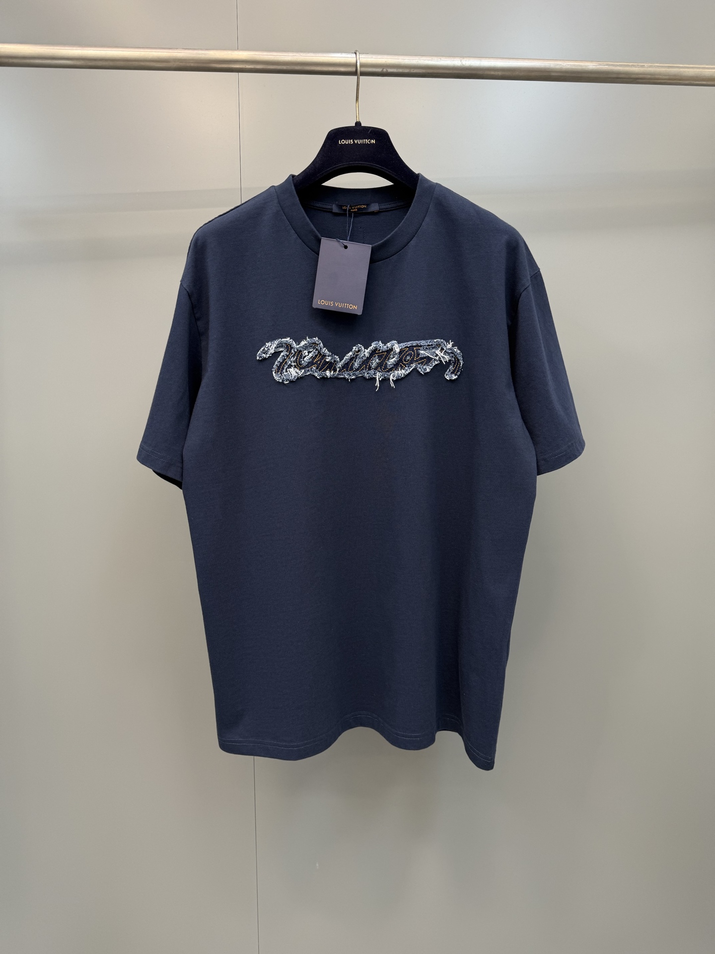 NO:823078,Lujia 26ss new patch-embroidered short-sleeved T-shirt is made of g-heavy combed cotton plain knit fabric, which is processed by garment washing process, giving the garment a soft and skin-friendly touch and a natural and soft retro texture, effectively improving the fabric's pilling resistance and dimensional stability. The body is cut with silhouetted shoulders, and is matched with a round neck and cuffs reinforced with two needles to achieve both comfort and durability. The core decoration on the chest  Using laser cutting patch + flat embroidery overlocking technology, the handwritten brand logo is precisely cut by laser, and the edges present a natural woolen effect, and are then fixed with flat embroidery with contrasting colors. The edge of the patch is sanded and scattered, forming a layered three-dimensional effect of rough edges. It has both craftsmanship details and visual tension. It is a model of the combination of street retro style and high-end ready-to-wear craftsmanship. Louis Vuitton - Clothing, louis  vuitton,louis vuitton,louis vuitton,T-shirt,tees,t-shirt,19860909驴家26ss新款贴布绣短袖T恤,甄选g重磅精梳棉平纹针织面料,经成衣水洗工艺处理,赋予成衣软糯亲肤的触感与自然柔和的复古质感,有效提升面料抗起球性与尺寸稳定性.衣身采用廓形落肩剪裁,搭配二本针加固工艺的圆领与袖口,兼顾穿着舒适度与耐穿性.胸前核心装饰采用激光切割贴布+平绣锁边工艺,手写体品牌标识经激光精准裁切,边缘呈现自然毛絮效果,再以撞色车线平绣固定,贴布边缘做磨毛散边处理,形成层次感丰富的毛边立体效果,兼具工艺细节与视觉张力,是街头复古风格与高级成衣工艺的结合典范,路易威登-服装,louis vuitton,louis vuitton,louis vuitton,T-shirt,tees，t-shirt,,Women's clothing