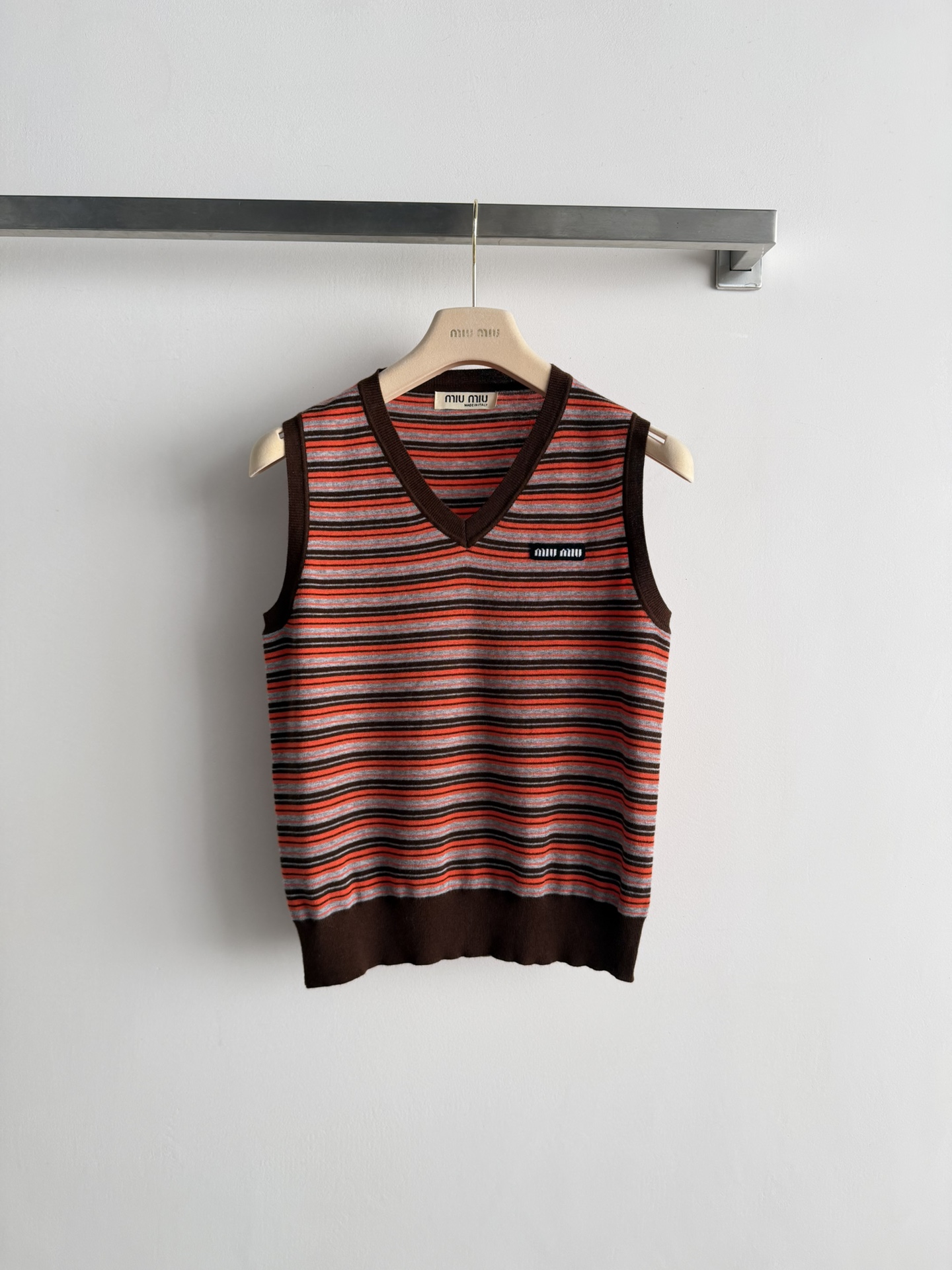 NO:731945,Miu Mi*26SS new striped V-neck vest, this striped V-neck vest is designed with horizontal stripes intertwined with red brown and dark gray, with a dark brown V-neck and hem, which is simple yet retro-modern. The letters on the chest are embellished with small letters, which are low-key without losing brand recognition. It is a versatile item in the spring and summer wardrobe that has both design and practicality. Whether worn alone or layered, it can easily create a fashionable look. SML,,miumiu,19860909Miu Mi*26SS新款条纹V领背心,这款条纹V领背心,以红棕、深灰交织的水平条纹设计,搭配深棕色V领与下摆,简约中透着复古摩登感.胸前的字母小标点缀,低调又不失品牌辨识度,是春夏衣橱里兼具设计感与实穿性的百搭单品.无论是单穿还是叠穿,都能轻松打造时髦造型.SML,,miumiu,,Women's clothing